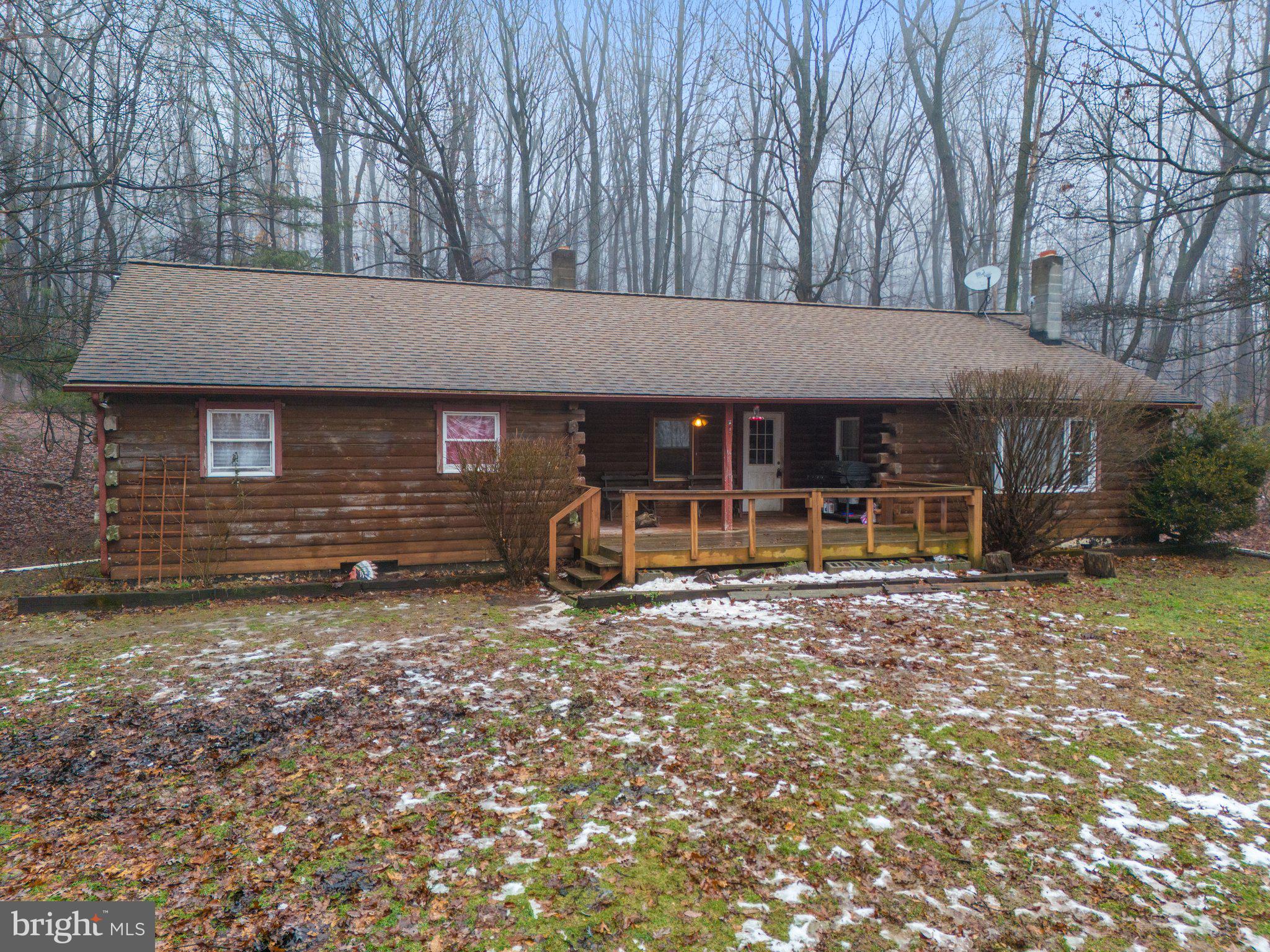 IT IS HIGHLY RECOMMEND TO WEAR BOOTS FOR WET AND MUD...................................Escape to the tranquility of this charming log cabin home, nestled on a private, 2+ acre lot near the end of a quiet dead-end street. A true oasis of serenity, this property offers a perfect blend of rustic charm and modern convenience. Step into the cozy living room, where a coal stove warms the space, creating a welcoming atmosphere that flows into the dining area. The kitchen, boasting a large pantry and convenient access to the rear yard, invites you to savor the joys of indoor-outdoor living. Down the hall, discover a generously sized bathroom and three bedrooms, offering a peaceful retreat for rest and relaxation. The basement unveils additional living space with a laundry room and two bedrooms. Apart from the bedrooms, the basement remains a canvas for customization—an unfinished space with a concrete floor and a wood stove, allowing your imagination to shape its future. The property is adorned with a detached 2-car garage featuring a second floor and a side door, adding both functionality and character to this enchanting retreat. A u-shaped driveway wraps around the back of the home, seamlessly tying into the main driveway and parking area, ensuring ease of access and ample space for guests. While this log cabin radiates charm, it presents an opportunity for personalization. The home requires a few new doors, trim work, some kitchen flooring, and repairs to two wall holes. The garage, a canvas for potential, needs rehabbed (roof, doors, second floor decking). Embrace the prospect of transforming this charming retreat into a personalized haven, where rustic charm meets the promise of renewal.  An inspection of the septic tank was completed om 1/26/24 and it is great working order.  A 50yr roof was put on in 2007.  Home is being sold As Is, however, seller is including a One Year Americas Preferred Home Warranty.