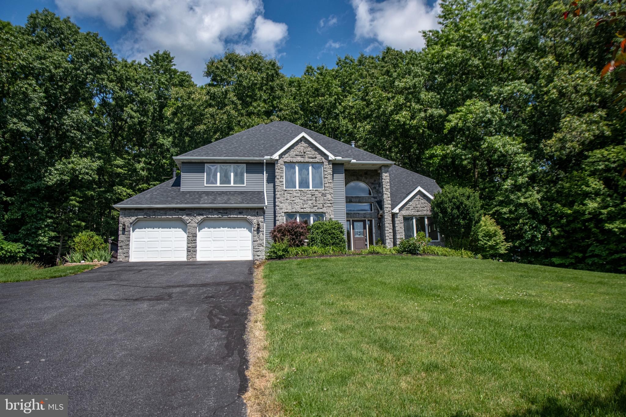 Welcome to this exceptional Bosak-built two-story estate, where timeless craftsmanship meets luxury living on 5.09 acres. This private, beautifully landscaped yard with Koi pond offers your own walking trails in the desirable Stormstown side of Halfmoon Township. From the moment you arrive, the tree-lined paved driveway sets the tone for this remarkable property offering elegance, serenity, and incredible versatility. Step inside the grand foyer, where soaring ceilings, rich hardwood floors, exquisite woodwork, and walls of windows fill the home with natural light. Just off the entrance, you'll find a private office that can easily serve as a main-level bedroom, along with formal living and dining rooms perfect for entertaining. The heart of the home is the stunning open-concept kitchen, featuring custom granite countertops, Bosh range/oven and dishwasher, abundant wood cabinetry, and seamless flow into the spacious living room. The upgraded gas fireplace creates a warm gathering space, while the adjoining sunroom offers peaceful views of the Koi pond with a water fall for living year-round. Upstairs, the luxurious owner's suite offers a spacious walk-in closet and an updated spa-inspired bath featuring a beautifully renovated custom shower and windows that flood the space with natural light. Two additional bedrooms and another full bath with a large sky light ceiling window complete the second floor, providing plenty of room for family and guests. The finished lower level expands the living space with a large family room, theater room, custom bar, full bath, and a fifth bedroom featuring its own private entrance—ideal for guests, extended family, or a home office.  An unfinished electrical room with newly installed tankless water heater and freezer complete this large lower level.  Outdoor living is equally impressive. Relax on the expansive paver patio overlooking the beautifully expanded koi pond complete with a tranquil waterfall, or unwind in the 20’ swim spa situated on a newer deck.  A just painted wrap around deck completes this home with a new 30 year warranty-roof. Every inch of the property has been thoughtfully designed to create a private backyard retreat. One of the property's most extraordinary features is the fully equipped second residence. This year-round guest house includes one bedroom, one full bath, a full kitchen, dining room, spacious living room, laundry, and gas and electric heat. This home offers an attached mini garage, making it perfect for multigenerational living, guest accommodations, or potential rental opportunities. Car enthusiasts, hobbyists, and entrepreneurs will appreciate the additional two oversized 25' x 25' garages with electric, providing exceptional storage and workspace year round.  A 20’ steel container is also situated for all your yard  care equipment. This one-of-a-kind estate combines luxury, functionality, and unmatched privacy in a breathtaking setting. With over five acres of picturesque grounds, quality Bosak construction, premium upgrades throughout, and a rare second home, this extraordinary Port Matilda property truly offers it all.