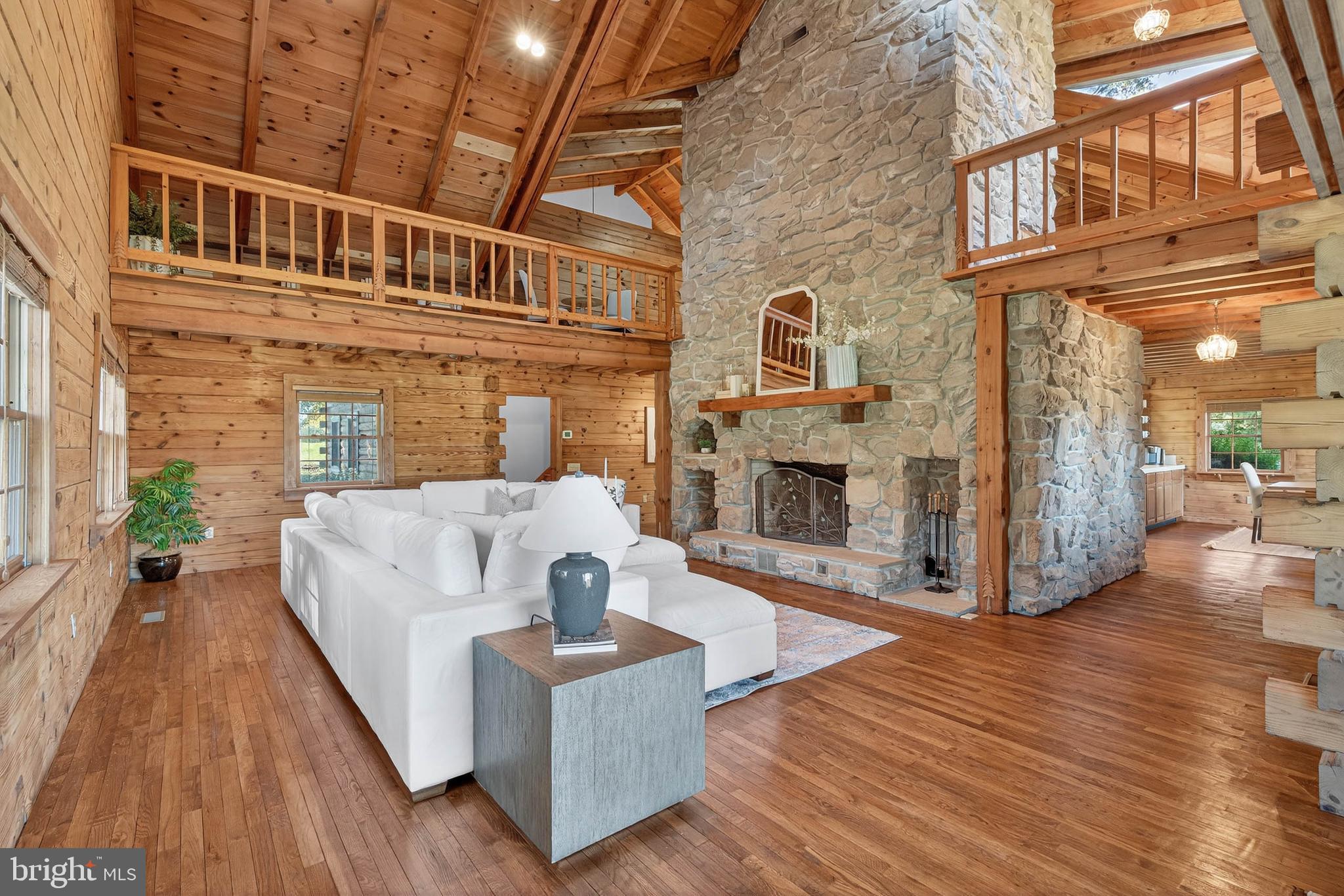 Experience timeless craftsmanship and modern comfort in this one of a kind, custom-built log cabin estate. An exceptional property that includes three separate parcels totaling four plus acres--the main homesite, a parcel with the above-ground pool and entertainment deck, and another parcel with a 36 ft x 60 ft horse barn featuring four stalls, tack room, wash pit, office, storage, and loft. Together, these parcels create a private retreat that blends rustic charm with luxurious living. Constructed from solid white pine D-logs with no 2x framing or siding, this true log home offers a warm and inviting atmosphere with structural post-and-beam construction throughout. Inside, gleaming hardwood floors, cathedral ceilings, and exposed beams frame spacious living areas designed for both comfort and entertaining. The great room impresses with a 16-foot-wide stone fireplace, twin balconies, and expansive windows that fill the space with natural light. The chef’s kitchen boasts granite counters, a gas cooktop, double ovens, custom oak and hickory cabinetry, a large island with custom seating, and a walk-in pantry. Enjoy scenic views in the bright dining area that overlooks manicured landscaping and countryside views, or enjoy a more intimate meal in the enclosed stone breakfast nook. The first-floor bedroom and full bath with clawfoot soaking tub provide flexibility for guests or main-level living. Upstairs, the primary suite is a true retreat with cathedral ceilings, a stone gas/wood fireplace, private screened balcony, large walk-in closet, and a spa-inspired primary bath featuring a four-person hot tub, glass shower, clawfoot soaking tub, skylights, and double vanity. An additional bedroom plus ensuite bonus room with cathedral ceilings and ample closet space complete the upper level. The fully finished basement offers over 2,000 additional square feet of versatile living space, including a recreation room with a regulation pool table, an exercise area, a large bedroom suite with full bath, a laundry room with washer/dryer hookup, mud room with drain and shower valve, office and bonus recreation space. Durable epoxy-coated floors and pine wainscoting provide both beauty and function. Enjoy panoramic country views from the two covered porches (8 ft x20 ft and 8 ft x40 ft), or relax by the 30-foot round swimming pool with multi-level decking, new pump, and filter system. Landscaped grounds include tiered flower beds, mature shade trees, and a three-tier goldfish pond with cascading waterfalls. A slate patio with open-air firepit, swing seating, and picnic area enhances the outdoor living experience. The home’s exterior has been freshly sealed (2025), and the roof was replaced with architectural shingles in June 2025. Additional features include an electrolux central vacuum on all three levels, central air, oil furnace, and outdoor wood stoker furnace for efficiency, 125-ft well with 32 GPM submersible pump, fireplaces feature heat-a-lators for enhanced warmth, ample parking and beautiful countryside surroundings. This remarkable property combines true log home craftsmanship with modern updates and outdoor amenities rarely found together. With three separately deeded parcels—including the pool and barn lots—this estate offers endless flexibility for living, entertaining, or future expansion. Schedule your private showing today and discover the peace, space, and elevated lifestyle this log home estate offers.
