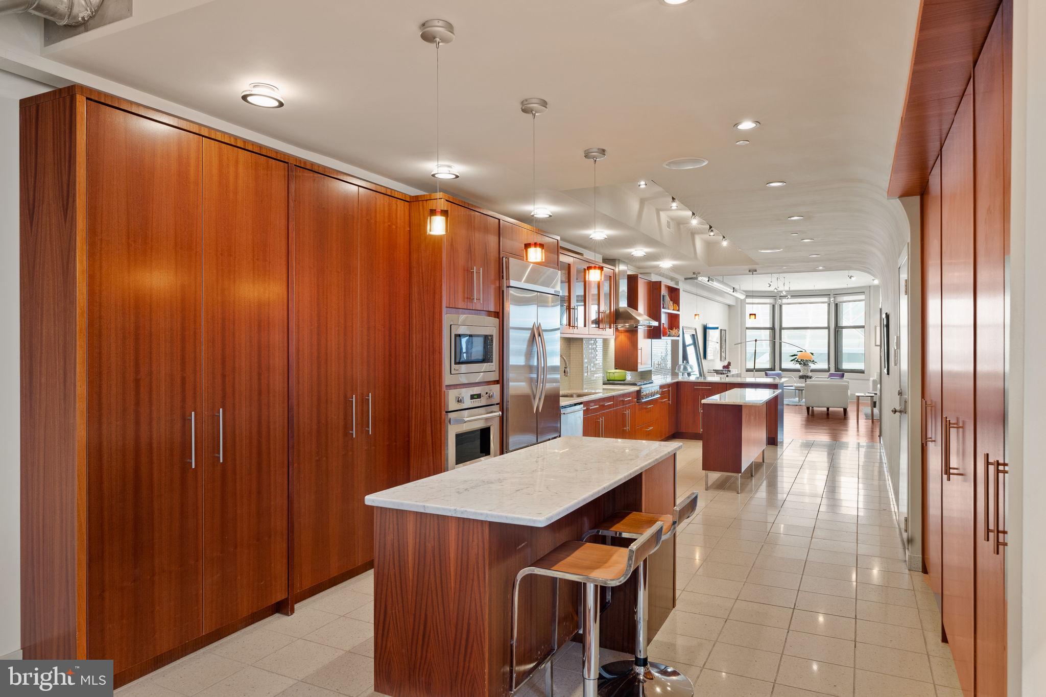 Refined single-floor living awaits in this masterfully curated, architecturally distinctive second-floor residence at 1606 Chestnut Street. Spanning approximately 2,500 square feet, this exceptional residence features a rare, elongated layout designed for effortless flow between multiple living and entertaining spaces. Every detail reflects a commitment to craftsmanship and design, with bespoke custom cabinetry and thoughtfully integrated built-ins throughout. The open and airy 19-foot wide living room is a true showpiece, highlighted by 9.5-foot ceilings, exposed brick and oversized bay windows flooding the space with natural light. At the heart of the residence is a remarkable 32-foot chef’s kitchen, impeccably designed with striking custom cabinetry, premium appliances, and elegant terrazzo tile flooring. Two center islands provide approximately 13 feet of counter space, making the kitchen ideal for entertaining, casual gatherings, and everyday cooking. Abundant built-in storage completes the space, seamlessly blending style and functionality. The formal dining area comfortably accommodates eight guests and is enhanced by a luminous light well, introducing an elevated architectural element and natural ambiance. Beyond, a spacious den and study with custom wood ceilings offer a rich, intimate setting ideal for relaxation or flexible work-from-home living. An integrated office nook provides a refined and functional workspace while preserving the room’s warmth and character. The primary suite is a private sanctuary, complete with dual walk-in closets and a spa-caliber en-suite bath featuring custom millwork, double vanities, a water closet and an oversized rain shower designed for ultimate relaxation. Currently configured as an expansive one-bedroom residence, the home offers the flexibility to seamlessly convert the den into a true second bedroom (reference the proposed layout in photo gallery) A thoughtfully designed floor plan is available for review in the photo gallery. Originally built in the 1890s by Isaac S. Miller and designed by architect Albert W. Dilks, 1606 Chestnut Street was notably advanced for its time, featuring two elevators and a central skylight that allows natural light to filter through the building. The interiors were crafted by master woodworker Francis D. Kramer, the building’s first tenant.. Ideally located just two blocks from Rittenhouse Square, this residence places you in the heart of Philadelphia’s most sought-after neighborhood, surrounded by renowned dining, boutique shopping, and vibrant city life. This address offers an elevated urban lifestyle where everything you desire is just steps from your door. One storage locker included in the sale.