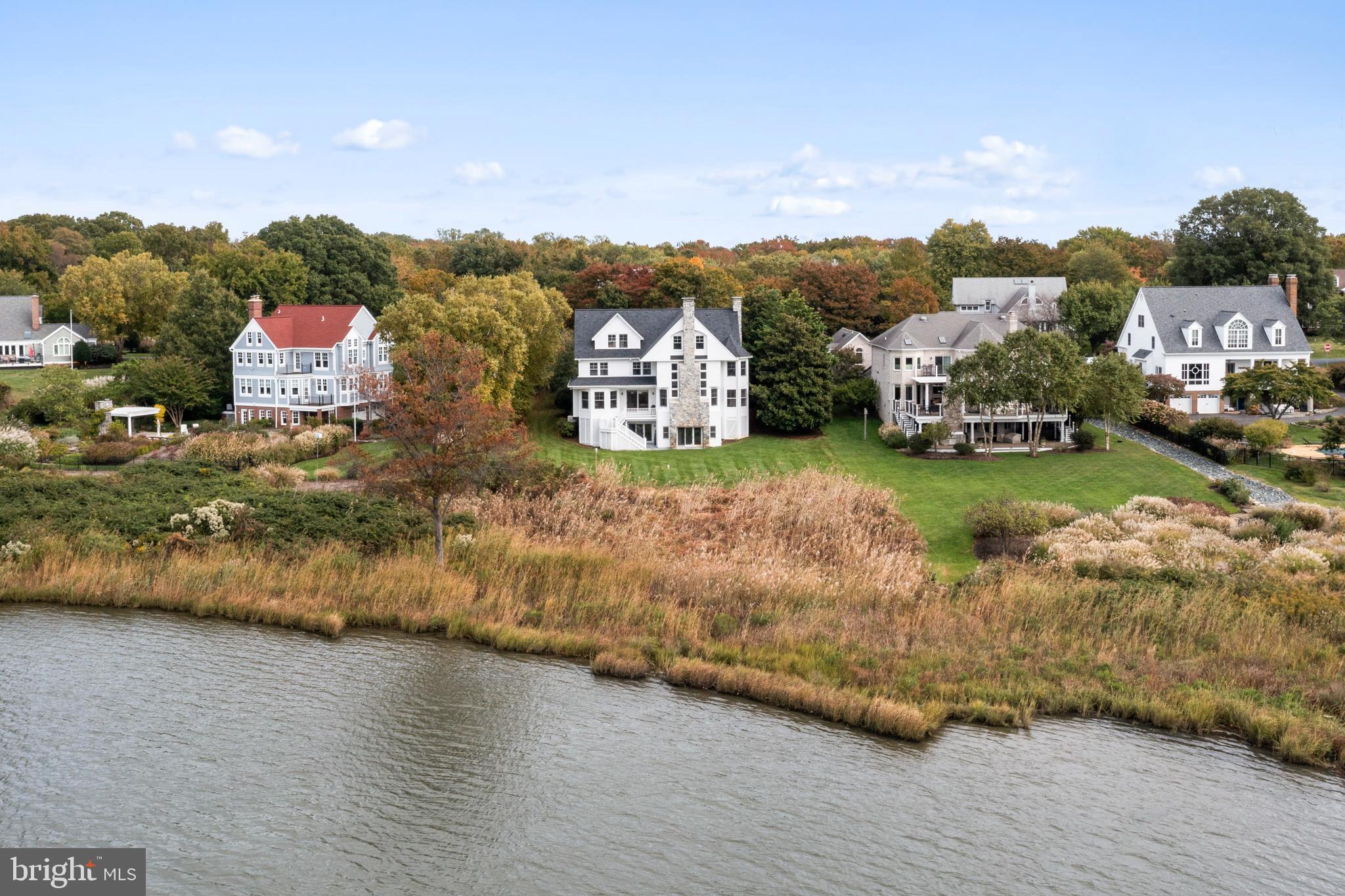 Glorious  water views and incredible sunsets from this custom-designed,  spacious home located in  sought after, amenity rich  Fishing Creek Farm. Move  right in to this updated  Victorian Farmhouse home with four finished levels of flexible living space, two magnificent 3-story stone chimneys plus a 3 car garage!  The majority of the rooms are strategically  designed to maximize  dramatic water views and the property adjoins community waterfront open space.   Original owners have recently remodeled  the kitchen with quartz countertops and island  offering a modern and stylish culinary space.  Water views greet you in  the  Great Room with a  dramatic stone fireplace, library/office with attached screened porch, family room, dining room, renovated kitchen. Main floor has two staircases, two powder rooms and  laundry.  Primary suite with  elegant new primary bath with luxurious features includes porcelain tiles, a soaking tub,  walk in shower, dual vanities and ample storage. Two additional bedrooms on the 2nd level with shared hall bath and new carpet.  3rd floor has two bedrooms, a hall bath,  two bonus rooms, and plumbing for another full bath. Walk out lower level has high  ceilings, a full in-law suite, a mini kitchen and laundry. Roof replaced in 2022, all  3 chimneys relined in 2023,  the  exterior and interior of the home was freshly painted in 2022/23,  Carpets replaced and hardwood  oak floors refinished in 2023.