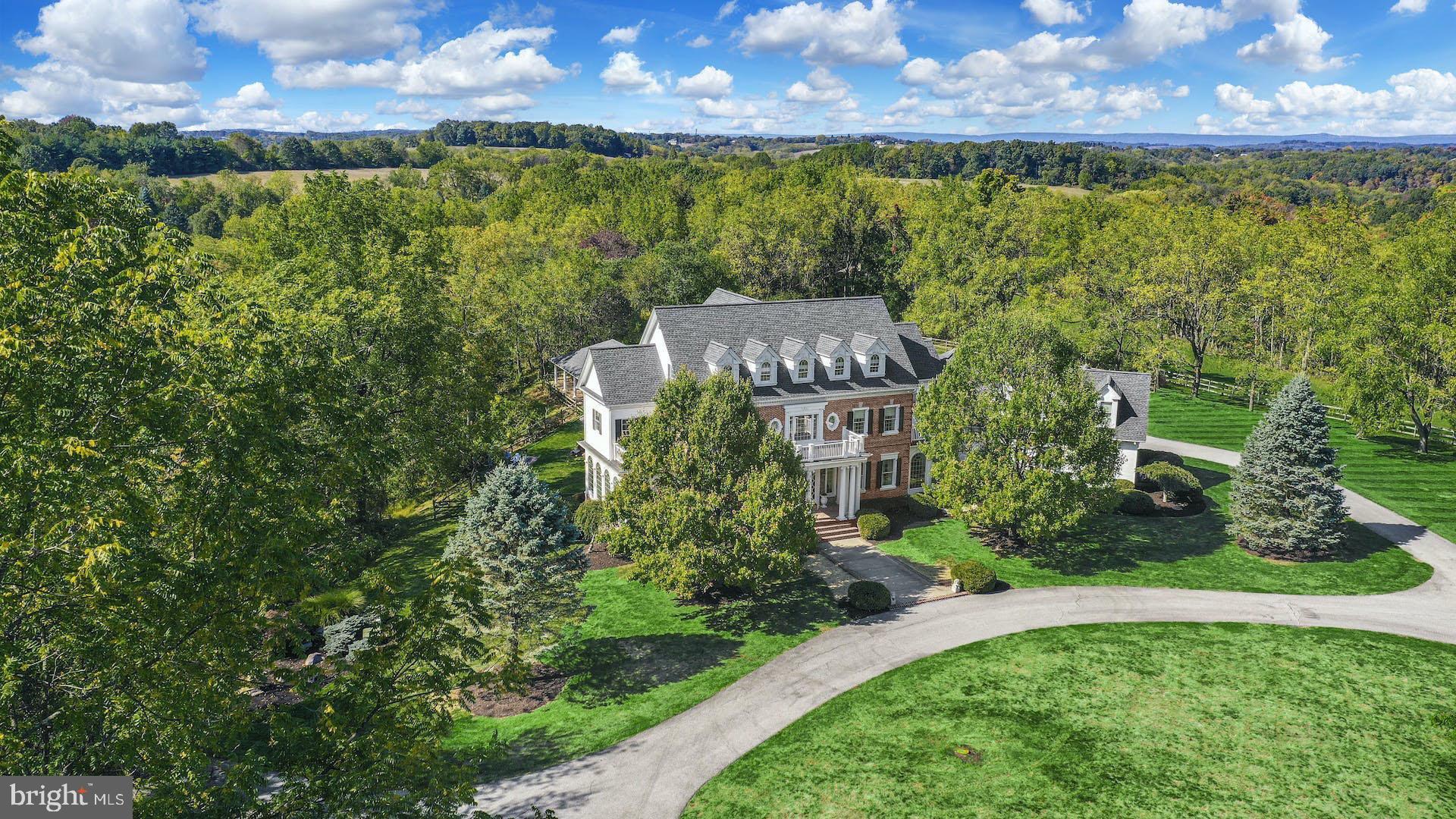 Located in the desirable Parkland School District, a picturesque, winding driveway brings you to this elegant country estate. Park Hill is set on over 13 acres, perfectly positioned atop a rolling hillside and bordered by mature trees and long-distance views.

With almost 8,000 square feet of living space plus an extensive lower level, this custom built home is an ideal setting for gatherings of all sizes. Oak floors and multi-tiered crown molding are found throughout most of the first floor, along with high ceilings and oversized windows. The Brader Woodcraft kitchen features granite countertops, Spanish porcelain tile backsplash, a 5 burner gas range, and a butler's pantry with beverage cooler by the nearby dining room. A formal living room, sunroom, office, spacious laundry room, and access to the 2022 deck are found on this level.

Upstairs, the primary suite is expansive, with a separate living room, dual walk-in closets, and access to a private balcony. The en suite bath includes a jacuzzi tub, glass shower, and dual vanities. Another suite and a step-up library with fireplace complete this floor. The third floor offers three large bedrooms and a full bath. More than 2,600 additional square feet of finished space are found in the walkout lower level, with a recreation room, exercise room, sauna, state of the art home theater, and guest suite.

The backyard is a lush playground, with a heated in-ground pool and hot tub. Chilly evenings are enhanced by a built-in fire pit on the deck of the nearby pool house.