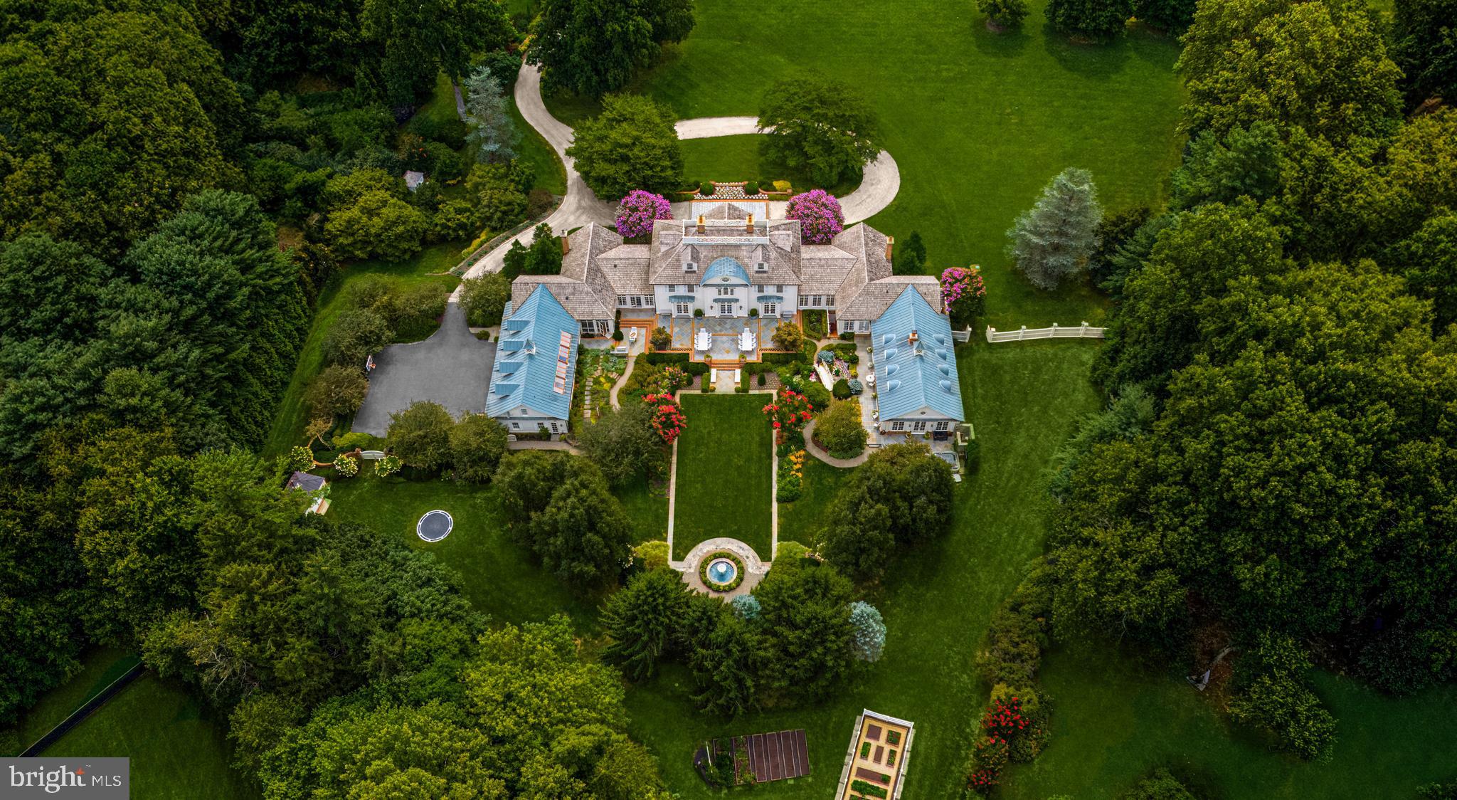 Gracefully sprawling across 4.56 manicured acres in Potomac’s coveted Golden Horseshoe, 9010 Congressional Parkway is one of the region’s premier estates. The residence embodies East Coast timelessness, blending the grandeur of expansive country manors with the tranquility of coastal retreats—all crafted to the highest finish level in the luxury space.  Originally designed by the esteemed architectural firm Versaci Neumann and painstakingly transformed by its current owners, the home underwent an exquisite restoration that introduced unique, imported finishes and bespoke elements from around the world, elevating its stature to new heights of luxury.

As you arrive, automatic gates part to reveal a meandering, newly laid driveway leading to a central motor court lined with pavers. The estate’s architectural significance is immediately apparent, with symmetry-driven design complemented by lush, tailored plantings. Federalist-style double doors open to a grand rotunda, introducing a gracious floor plan spanning 15,451 square feet of sophisticated living space.

Formal rooms radiate from the grand foyer. The living room extends 34 feet, anchored by a roaring fireplace and lighted, molded built-ins shimmering against lacquered walls and ceilings. A marble wet bar with smoked mirrors connects to the custom-paneled sitting room, which opens to gardens via French doors.

The informal areas carry a coastal flair, starting with the chef’s kitchen, where soaring beamed and shiplap cathedral ceilings frame the space and whimsical antique theater lights imported from Paris are a show-stopper above the oversized center island.  Redundant commercial-grade appliances are nestled within furniture-grade inset cabinetry and waterfall countertops. The adjacent family room features a mirrored ceiling design, masonry fireplace, and chair rail moldings that complement built-ins, creating an intimate yet expansive atmosphere.

The solarium and garden cutting room dazzles with inlaid marble floors, built-in planters, and intricate latticework, seamlessly connecting to the outdoors, storage areas, and mudroom. On the opposite end of the main level, the private primary retreat boasts soaring ceilings, a gas fireplace, and a sitting room with direct outdoor access. The marble-clad ensuite rivals world-class resorts and is paired with two dressing rooms, each with a center island. Directly connected to the suite is a spectacular game room with cathedral-beamed ceilings, a masonry fireplace and custom paneling, leading to a fitness center that opens to an outdoor terrace with a spa and shower.

The second floor features four spacious bedrooms and three baths surrounding the rotunda. A third-floor suite enhances versatility, while a separate apartment above the four-car garage offers additional accommodations.

The lower level centers on entertainment, with a large recreation room, wet bar, and private cinema professionally designed with tiered seating and high-end equipment for an unparalleled viewing experience.

Outside, the estate’s meticulously maintained grounds draw inspiration from grand European properties, blending hardscaping with exquisite landscaping. Features include a koi pond, trickling fountain, vegetable gardens, and four separate sheds, creating a serene, natural oasis.

Supported by industrial-grade systems rarely seen in a residential setting, the estate is a fortress of luxury. Conveniently close to Washington yet offering complete seclusion, 9010 Congressional Parkway stands as a globally distinguished estate, embodying impeccable craftsmanship and timeless elegance.