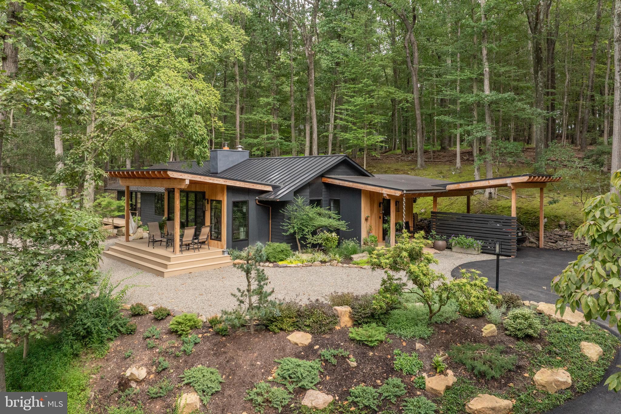 Nestled within the greenery of New Hope, an extraordinary retreat is tucked away- welcome to Moss Hill. This property is a fully revived Mid-Century Modern home, designed by Chris Pickell & Associates, and meticulously renovated in 2024, sparing no expense. Each component of the home was thoughtfully deliberated, merging classic architectural design with state-of-the-art systems, energy-conserving enhancements, and bespoke finishes. The house was stripped down to its bare studs and reconstructed with brand-new electrical systems, high-grade PEX plumbing with manifold, efficient HVAC systems, foam insulation, and superior Marvin Elevate windows and doors. Elegant laminated beams arch the ceilings, while expansive 8' x 12' sliding doors admit an abundance of light and a sense of the outdoors. Modern steel elements, Hardie board siding, a standing-seam metal roof, and Douglas Fir porch features contribute to the home's distinctive curb appeal. Within, the layout is characterized by smooth lines and open spaces. The kitchen, equipped with custom Plato cabinetry constructed from Shou Sugi Ban, a Wolf induction cooktop, a Wolf M Series oven, a Bosch refrigerator, a Fisher Paykel drawer dishwasher, and a bar area with charred wood accents, is the center of the home. A pair of Velux skylights wash the space in natural light, while a stunning wood-burning fireplace with a customized steel surround adds warmth and aesthetic appeal. Every room exudes luxury and thoughtful design. Mirage white oak engineered floors extend throughout the home. The bathrooms provide an experience akin to a luxury spa, with Grohe curb-less showers, heated floors, Robern anti-fog mirrors, towel warmers, and Japanese-style bidet toilets. The master bath is a haven of tranquility, while a unique stone Japanese soaking tub is a highlight of the guest bath. Custom-designed closets by Closet Works add to the home's appeal. In terms of technology and convenience, the home is equipped with a whole-house WiFi system, Honeywell smart thermostat, Bosch high-efficiency heat pump, Briggs & Stratton whole-house generator, reverse osmosis filtration, and a Bradford White heat pump water heater. Soundproofing and insulation were also upgraded beyond standard. The in-house and outdoor living experiences at Moss Hill are equally impressive. Several Azek composite decks extend from the living room and master suite, overlooking panoramic woodland views. A spacious bluestone patio with integrated drainage, newly landscaped grounds, and bold boulder features create an ideal environment for entertaining. The completely renovated gunite swimming pool (2025) boasts new systems, stone decking, and a revitalized pool house with a privacy screen and deck. Moss Hill's prime location is just minutes away from boutique shopping, exquisite dining, river activities, The Bucks County Playhouse, and is an easy 80-minute drive from NYC and an hour from Philadelphia. Combining the charm of mid-century modern architecture with modern efficiency, sustainability, and luxury, Moss Hill offers a unique living experience in an organically peaceful & private setting.