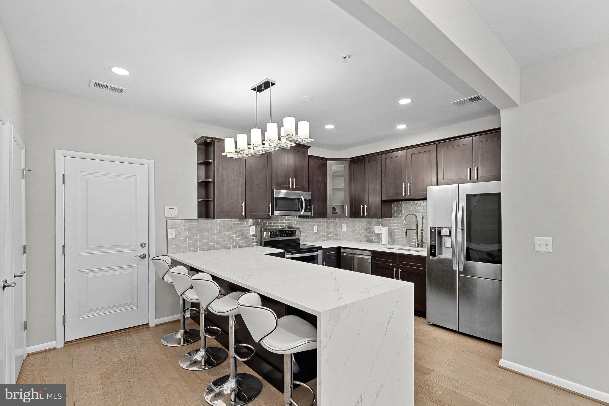Welcome to this modern two-level townhome style condo in the heart of One Loudoun! Experience one of the rare, truly walkable lifestyles in Loudoun County, with restaurants, cafés, shopping, entertainment, a movie theater, and more just steps from your front door.Step inside to the main level, where you are greeted by an open and spacious living room featuring stunning engineered hardwood floors and fresh paint throughout, giving the home a bright and refreshed feel. Adjacent to the living area is the beautifully updated kitchen, showcasing sleek waterfall quartz countertops with bar seating, a stylish backsplash, stainless steel appliances, a pantry, and modern cabinetry offering ample storage space. The main level also provides direct access to the attached one-car garage and private driveway.Upstairs, you’ll find three bedrooms and two bathrooms, including a spacious primary suite featuring two walk-in closets and a luxurious en-suite bathroom complete with a vanity offering generous counter space, a walk-in shower, and a private water closet. Two additional bedrooms are located on the upper level, including one with direct access to the balcony. The washer and dryer are also conveniently located upstairs. Brand-new carpet throughout the upper level adds a fresh finishing touch.Residents of One Loudoun enjoy access to exceptional amenities through the One Loudoun Club, including an outdoor pool, indoor half basketball court, pickleball courts, tennis courts, scenic trails, outdoor exercise areas, and more.The location is truly unbeatable, within walking distance to Trader Joe's, Alamo Drafthouse Cinema, popular dining options, shopping, cafés, and entertainment. Commuters will appreciate easy access to Route 7, Route 28, the Silver Line Ashburn Metro Station, and Dulles International Airport. This home truly has it all. Schedule your showing today!