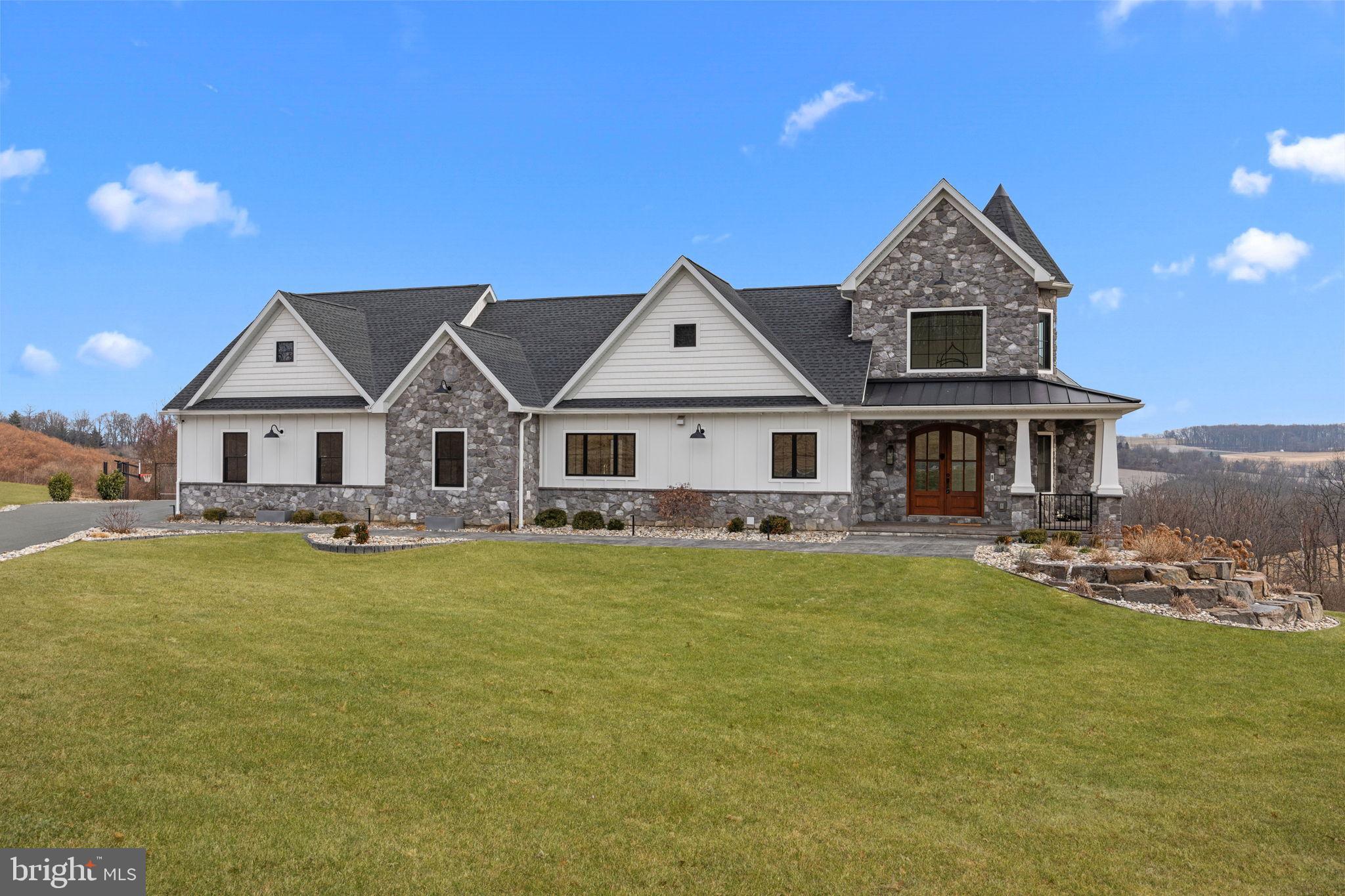 Welcome to 176 Fenstermacher Road, an exceptional custom-built estate by European Builders, perfectly situated on 3 private acres with stunning hillside views in Kutztown. This home seamlessly blends refined craftsmanship, advanced technology, and resort-style living. The heart of the home is a chef’s kitchen featuring GE Café appliances, custom Woodmont cabinetry, a hidden walk-in pantry, and generous prep space, all filled with natural light from Pella windows and enhanced by vaulted ceilings. The residence offers six bedrooms, all with custom closet systems, along with three full and two half bathrooms, and dual-zone heating and cooling for year-round comfort. The three-car garage connects directly to a private home gym, while the lower level delivers a spa-like experience with a steam room and sauna. Additional highlights include a whole-house sound system, smart blinds, EV charging hookup, two Elkay bottle fillers, a Generac whole-house generator, and a thoughtfully designed mudroom with a dog shower and dog bowl water-filling station. Step outside to your own private resort featuring a saltwater pool and spa, water feature, custom fire pit, half-court basketball and tennis court, and a custom Amish-built playground, all set against peaceful countryside views. A 1,000-gallon propane tank provides efficiency and reliability. A rare opportunity to own a meticulously designed luxury home offering privacy, recreation, and elevated living in one of Kutztown’s most scenic settings.