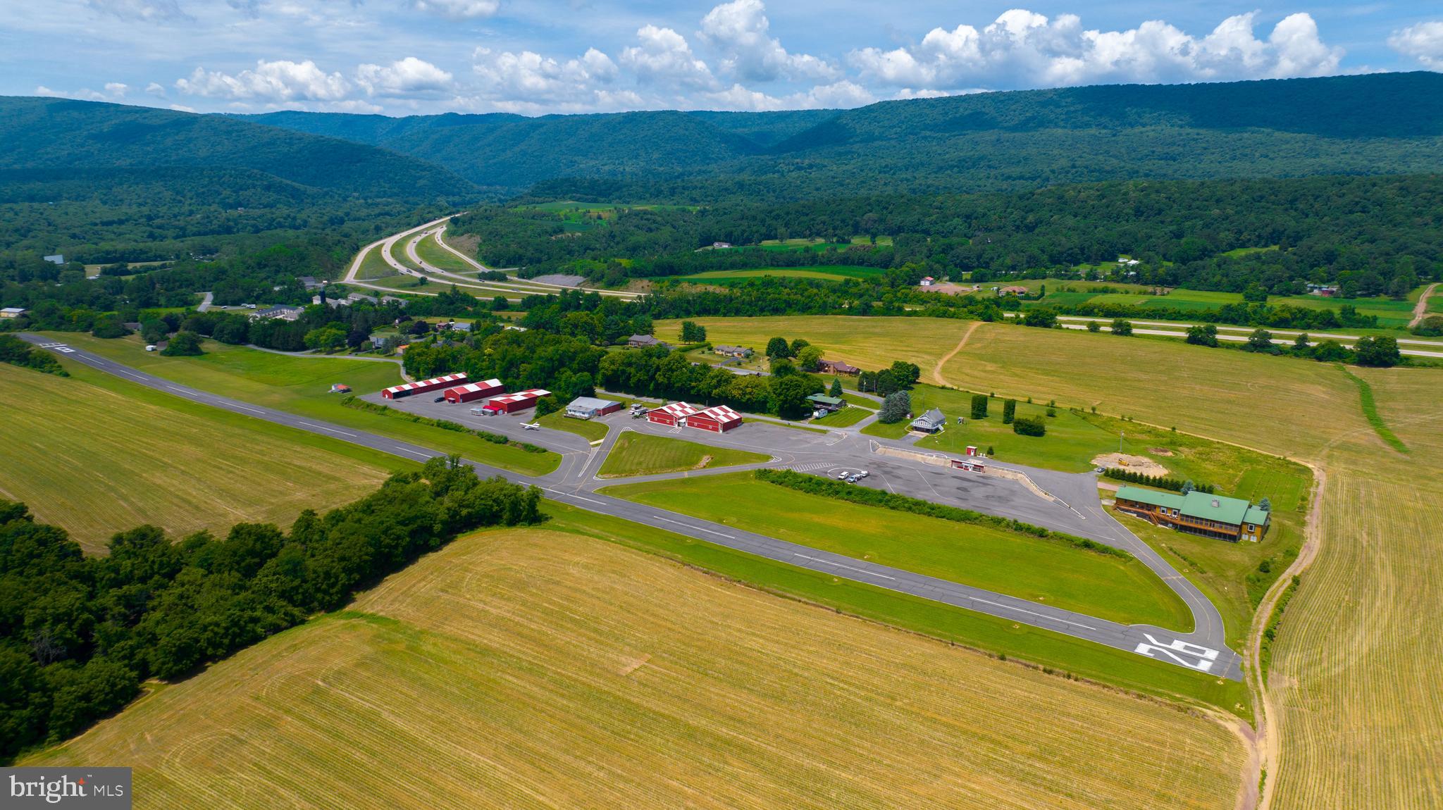 You are cleared for landing! Welcome to Mifflintown Airport, a 24-acre private oasis in Juniata County, surrounded by a peaceful setting of scenic mountains, serene farmland, and the Juniata River is just a couple blocks away. The property is conveniently located between Harrisburg and State College/Penn State University. The property is highlighted by a 2,650-foot paved and lighted runway with a GPS approach, a custom 12,000 plus square foot owner's home that has a brand new enclosed in-ground pool for year-round enjoyment, over 23,000 square feet of hangars, 6,000-gallon fuel storage, two residential rental properties, an apartment, and an additional residential home that can be redeveloped into a hangar home. Mifflintown Airport is unattended and based aircraft owners are extremely helpful in maintaining the facility. The airport can handle most turboprops. The local RC airplane club is also based at the airport. Mifflintown Airport is only 140 air miles west of Teterboro Airport in New Jersey, 145 air miles from Northeast Philadelphia Airport, and a 55-minute drive to Harrisburg International Airport. The airport features 23,000 square feet of hangars in 13 different units. Three of these hangars (9,400 square feet) are heated. The airport has 6,000 gallons of fuel storage set up for two fuels. The property offers 3.5 acres of undeveloped land as well. The owner's home, sitting on 2.2 acres and separately deeded, was completed in 2008 and is 12,000 plus square feet, including 9,800 square feet on two floors, a 1,600 square foot heated garage that can be opened to 37 feet of free span, and a 1,504 square foot screened-in porch. Many windows and glass doors offer unlimited opportunities to enjoy the surrounding views. Hardwood floors can be found throughout. The home is set up with four bedrooms with a potential to add two bedrooms with a Jack and Jill bath in the lower level. The owner's suite includes a cedar lined walk-in closet, a whirlpool tub with a bay window, and an oversized walk-in shower. The lower-level bedroom has its own bath with a jacuzzi tub and walk-in shower. The home has an additional full bath too. The modern kitchen boasts oak cabinets and granite countertops. Stainless steel appliances include a large gas cooktop with grill and griddle, and a warming drawer. The main living room boasts a vaulted wood ceiling and a pellet stove in a stone chimney encasement. The full, finished lower level provides a home theater, fireplace, cedar lined closet, and a large area for various recreational activities. The complete U.S. sectional map is epoxied into the floor. A covered front porch surrounds the front of the home while a rear deck encases the back with a covered area next to the kitchen for year-round grilling. Outside, a new vineyard was planted in 2019. The owner's home comes with an alarm system, a video system, a separate RO water system, a telephone system and high-speed internet great for a remote office. The residence has two air conditioning systems and is completely heated with automatic wood pellet fired boilers. There is potential to build a hangar and a housekeeper apartment on the owner’s lot as well. Don't wait to schedule your visit and see this amazing property with your own eyes today!