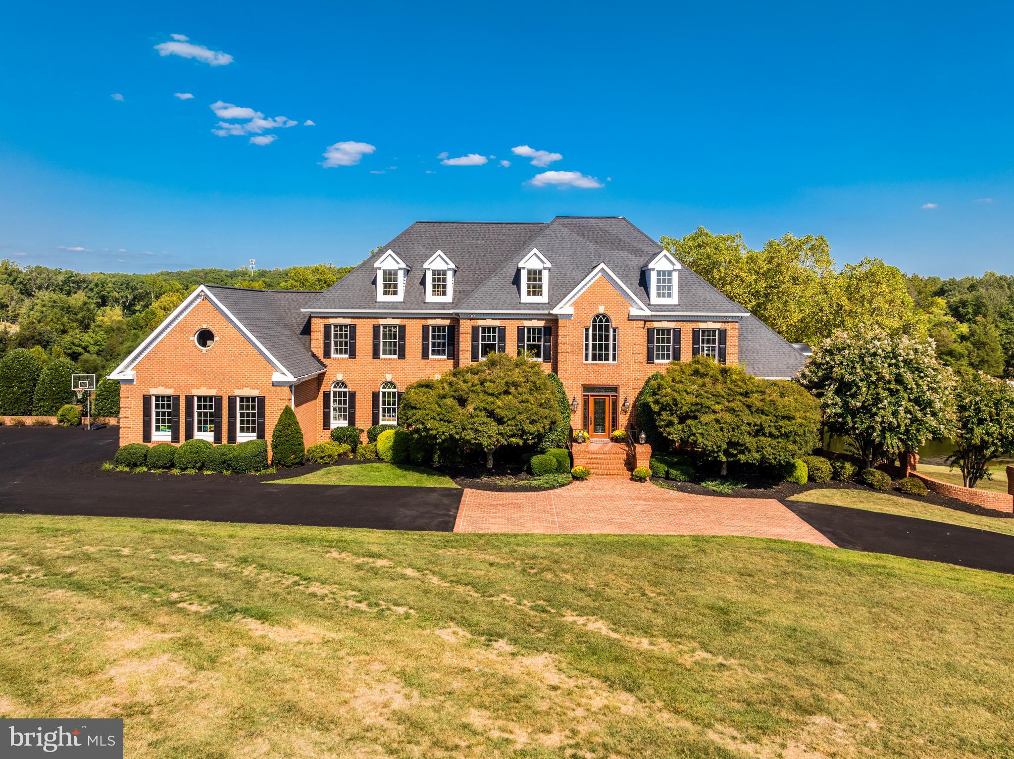 ***Motivated Sellers as they have found their home of choice***Commanding 3+ idyllic acres with two tranquil ponds and majestic mountain views in the luxury enclave of Barclay Ridge, this countryside estate offers premium outdoor entertaining and opulent interiors with expansive en suite bedrooms, all in a peaceful retreat-like setting just minutes from local amenities and commuter routes. Timeless brick architecture and a grand front entry set the tone, welcoming with a circular freshly paved driveway leading to the oversized 3-car side-load garage. Arrive into a two-story, formal foyer joined by the front parlor and formal dining spaces. A sunroom with vaulted, open-beamed ceilings captures natural light on three sides and showcases breathtaking views of the landscape. Enjoy a private home office with built-ins and a bay window, adjacent to a spacious powder bath. The gentle step down into the family room invites you to relax and gather around the floor-to-ceiling stone fireplace, and exterior doors on each side open out to the expansive deck that spans the entire rear length of the home. Designed for entertaining, the gourmet chef's kitchen hosts a generous granite countertop and breakfast-bar island, updated premium wood cabinets, high-end appliances, and a large walk-in pantry for additional storage. The open layout flows seamlessly into a sunlit eat-in dining space, perfect for casual meals, cocktails and conversation around the corner fireplace which connects to the spacious mud room and laundry room with updated cabinets as well. Hardwood floors, freshly polished, grace the main level, and exquisite moldings and mantels evoke visions of an old-world estate, set apart and modernized by the grand scale of the home’s contemporary design and thoughtful creature comforts. Upstairs, retreat to your palatial primary suite featuring a tray ceiling, a private sitting room retreat with fireplace and built-ins, and a dressing room style walk-in closet. Indulge in the spa-like completely remodeled primary bath with dual marble vanities, walk-in shower, and a corner soaking tub framing the treetop views. Additionally, there is a bonus room perfect for a studio/nursery/workout room or office space with complete privacy.  Three additional generously sized bedrooms, each with a walk-in closet and private full bath en suite, complete the upper level. The finished, daylight lower level walks out directly to the covered patio, seamlessly blending indoor and outdoor living spaces. Cozy up in the rec room with a stone fireplace, and entertain in the well-equipped brand new kitchenette, complete with new flooring, fridge, dishwasher, sink, storage and bar seating. Versatile spaces abound, including a library lounge with built-in bookshelves, a game room, a bonus room perfect for an office or gym, plus a storage/utility room with a second washer and dryer. A full bathroom and spacious 5th bedroom on this level provide even more flexibility for family and guests. Fresh paint throughout parts of the home. Tucked in the private countryside of coveted Barclay Ridge, yet easily accessible to all the best of Loudoun County, this location is like no other. Enjoy nearby shopping at the Leesburg Outlets, One Loudoun and Brambleton Town Center, and easy access to Loudoun County Wine Country, commuter routes and Dulles International Airport. From the idyllic location to the stunning landscape to the luxurious amenities, this estate offers an unparalleled lifestyle. A rare opportunity not to be missed.