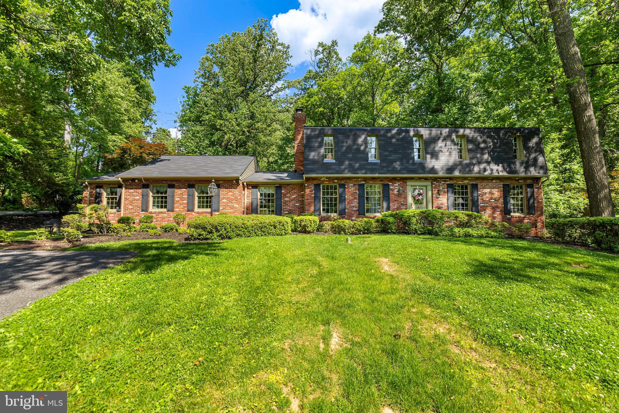 This well constructed Dutch Colonial is elegantly situated on an elevated lot in Summer Hill, a desirable Phoenix location. The house has been expanded to include a primary bedroom suite on the main floor with a luxury bathroom, its own laundry, and a spacious walk-in closet with custom built-ins. The second floor includes four additional bedrooms, one with  an en-suite bathroom, a hall bathroom and a second laundry. 
The kitchen opens to an expansive  family room with 2 sets of French doors opening to the surrounding decks. Natural light fills the room which also has vaulted ceilings, and a fireplace. The home features hardwood floors throughout. The finished lower level includes a bar and built-ins, a full bathroom and ample storage.  A detached, oversized brick two-car garage offers additional storage. For summer entertaining, two outdoor living spaces open onto a lovely, flat, manicured yard. The original stone spring house, part of the initial estate property sits ideally on the front yard and is constantly admired by neighbors and passersby and adds to the charm of this exceptional property.
