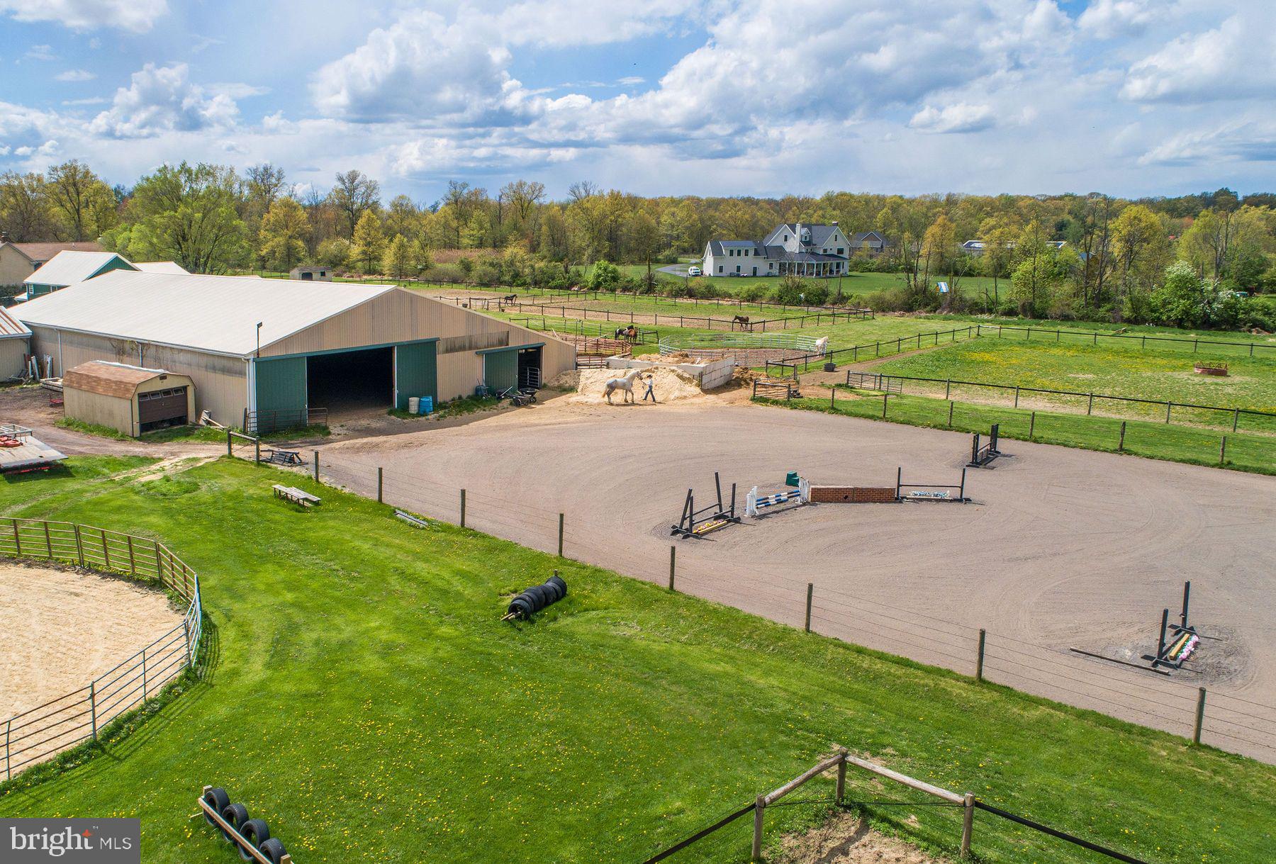 This classic Bucks County farmhouse estate offers a rare opportunity to own a fully equipped equestrian property set on nearly 13 picturesque acres in Hilltown Township. Designed with the serious horse enthusiast in mind, the property seamlessly combines a turnkey training facility with the timeless charm of a circa-1780 farmhouse—creating an ideal setting for both horse and rider.
At the heart of the farm is a 60' x 120' indoor riding arena, thoughtfully updated with masonry sand and fiber footing for optimal performance. Complementing the indoor is a 100' x 200' outdoor arena with well-draining footing, providing year-round versatility for training and riding. The well-appointed barn features 23 horse stalls, 4 pony stalls, and a two-stall shed row, along with two tack rooms, a kitchenette, and a bathroom for convenience. Eleven fenced pastures with solar-powered electric fencing allow for efficient rotation and turnout, while a round pen and hot walker support a complete training program. A private trail encircles the pastures, offering the ease of riding directly on your own property.
Above the barn, two beautifully updated apartments—one one-bedroom and one two-bedroom—provide excellent options for staff housing, guest accommodations, or rental income. One includes an enclosed porch, while the other offers a flexible bonus room.
The farmhouse itself overlooks the grounds, offering peaceful views of the pastures and daily horse activity. A welcoming wraparound front porch sets the tone, while inside, the home blends historic character with modern comfort. Wide-plank yellow pine floors, deep window sills, and exposed beams reflect its heritage, while the thoughtfully designed layout supports today’s lifestyle.
The living room features a striking stone fireplace with wood insert, and the dining room includes a built-in mirrored serving cabinet and generous storage. A dramatic floor-to-ceiling stone wall anchors the kitchen, which is equipped with cherry cabinetry, granite countertops, stainless steel appliances, and a bright breakfast area.
The family room, with its raised-hearth stone fireplace, opens to a private 530-square-foot two-tiered deck—perfect for relaxing or entertaining while overlooking the pastures. A mudroom with laundry, located on the barn side of the home, provides a practical transition from stable to house.
Upstairs, the primary suite offers a walk-in closet and a spacious bath with dual vanities, Jacuzzi tub, and separate shower. Three additional bedrooms and a full bath complete the second floor, while a walk-up attic offers expansion potential.
Additional highlights include a new roof (May 2024), updated HVAC systems (2022/2023), a newer oil tank and heater flue, and an electronic dog fence encompassing approximately six acres.
Beyond equestrian use, the indoor arena can easily accommodate storage for equipment, vehicles, or recreational boats. An adjacent equipment shed and a heated/cooled 1.5-car garage with 220 three-phase electric, high ceilings, and bright LED lighting make this property equally appealing for hobbyists or small business use.
Ideally located in the heart of Bucks County—just 5 miles from Dublin, approximately 18 miles from the Bucks County Horse Park, 35 miles from Philadelphia, and 80 miles from New York City—this property offers the perfect balance of accessibility and a private country setting.
Act 319 preferential assessment, which may allow for a one-acre subdivision, offering potential for a second homesite (buyer to verify). 24-hour notice required.
