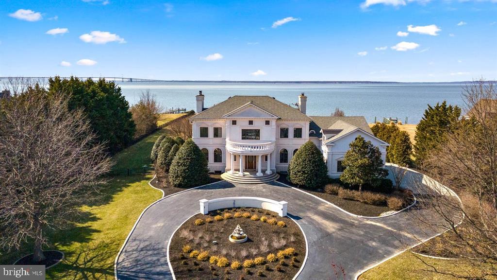 Nestled within the prestigious Wolf Farm community, this exquisite residence offers a harmonious blend of luxury and comfort, perfect for those seeking an elevated lifestyle. This property is one of few on Kent Island that has unobstructed views of Annapolis, Baltimore and the Chesapeake Bay Bridge. Guests are welcomed with a gated circular drive adorn with stone pillars, lush flower beds and a professionally manicured lawn. The neoclassical architectural style mimics that of Thomas Jeffersons home Monticello.   Spanning an impressive 10,152 square feet, the kitchen has been meticulously renovated in 2026, ensuring convenience of use while gazing at the Bay. Step inside to discover an open floor plan that invites natural light to dance across the stunning marble and luxury vinyl plank flooring. The eat-in kitchen and separate formal dining room provide ample space for entertaining, while the pantry ensures that all your culinary needs are met. The primary suite is a true sanctuary, boasting a bay-front view, a lavish primary bath, and expansive walk-in closets. Each of the nine bedrooms is designed with comfort in mind, offering generous space and thoughtful details. With eight full bathrooms, morning routines are a breeze, ensuring privacy and convenience for all. The heart of the home is complemented by three elegant fireplaces, creating cozy nooks for relaxation. Recessed lighting and upgraded countertops throughout add a touch of sophistication, while the wet/dry bar and custom wine cellar elevate your entertaining experience. Step outside to your personal oasis, where a stunning in-ground pool awaits, surrounded by multiple terraces and balconies that overlook the serene Chesapeake Bay. With 500 feet of waterfrontage, this property offers unparalleled access to the water, complete with a private composite dock that accommodates multiple slips for your boating adventures. Whether you enjoy power boating or kayaking, the navigable waters provide endless opportunities for exploration. Additional features include a full daylight basement with outside access, perfect for guests or recreational activities, and an attached side-entry garage with ample driveway space for up to 15 vehicles. This home is not just a residence; it's a lifestyle. Experience the tranquility of waterfront living combined with the luxury of modern amenities, all within the embrace of a warm and inviting atmosphere. Embrace the exclusive lifestyle that awaits you in this remarkable property.
