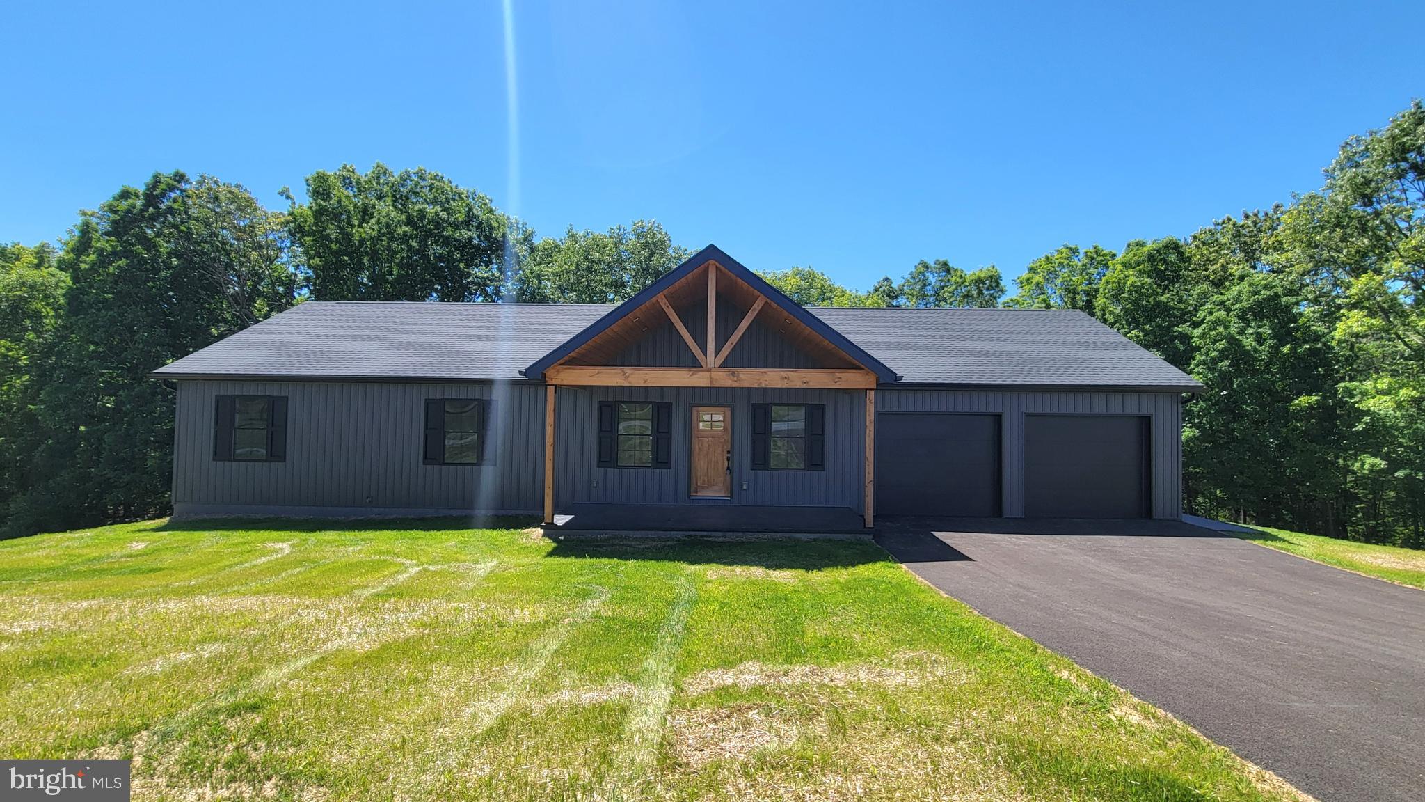 Brand New & Ready For You - Stunning new construction contemporary rancher with 2,980 finished sq feet living space.  Perfectly situated on 3.5 private acres backing to woods for privacy.   Designed with an open floor plan, this home offers 4 spacious bedrooms and 3 full bathrooms, ideal for both everyday living and entertaining.    Inviting great room featuring exposed beamed cathedral ceilings, creating a bright and airy atmosphere.  The gourmet kitchen is a showstopper, complete with granite countertops, a large center island, and stylish pendant lighting.   A convenient main-level laundry room with built-ins adds to the home’s thoughtful design.  Master bedroom suite has 2 walk-in closets, delightful soaking tub and walk-in shower.    Love that fully finished walk-out basement—perfect for a recreation room, home gym, or flexible use to suit your needs.   Enjoy outdoor living at its best with a maintenance-free deck and a lower-level rear patio, offering multiple spaces to relax or entertain while taking in the peaceful natural surroundings.    Double garage with finished interior and lots of recessed lighting.  Located just minutes from I-70, and only 5 minutes to the C&O Canal towpath, the Potomac River, and Hancock's small-town charm, this property offers the perfect blend of privacy and convenience.    Quality built by local contractor. driveway has been paved and grass is growing.    Just 20 minutes west of Hagerstown and 3 miles off I-70.  Move in and enjoy a fabulous new home, priced to sell!