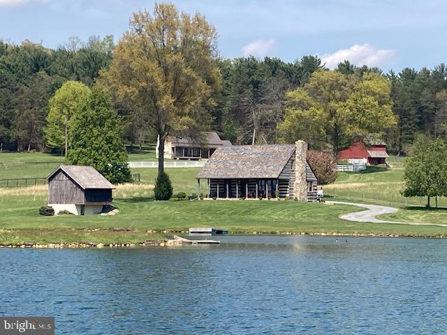 THIS PROPERTY IS GOING TO AUCTION ON THURSDAY JULY 16, 2026 AT 6:00 PM. THE LIST PRICE ONLY REFLECTS THE SUGGESTED STARTING BID.  9.32-acres with an outstanding custom-built rustic log home overlooking your own private 3-acre pond with island. Inviting front porch for relaxing and enjoying the tranquil setting. Home features a galley-style kitchen with breakfast nook, living room with brick fireplace, formal dining room, covered flagstone front porch. 3 bedrooms, 2 full bathrooms. Improved lower level with a family room and huge brick fireplace plus a utility room. Central AC/heat pump, 200 amp service, spring water and on-site septic. 2-tracts selling as one, 1.77 acres plus 7.55 acres. Outbuildings include a 16' x 18' 2-story working springhouse, 8' x 12' garden shed and a working windmill. Ample space for your animals or pets. Truly a must see type of property located just south of Himes Hill New Holland.
