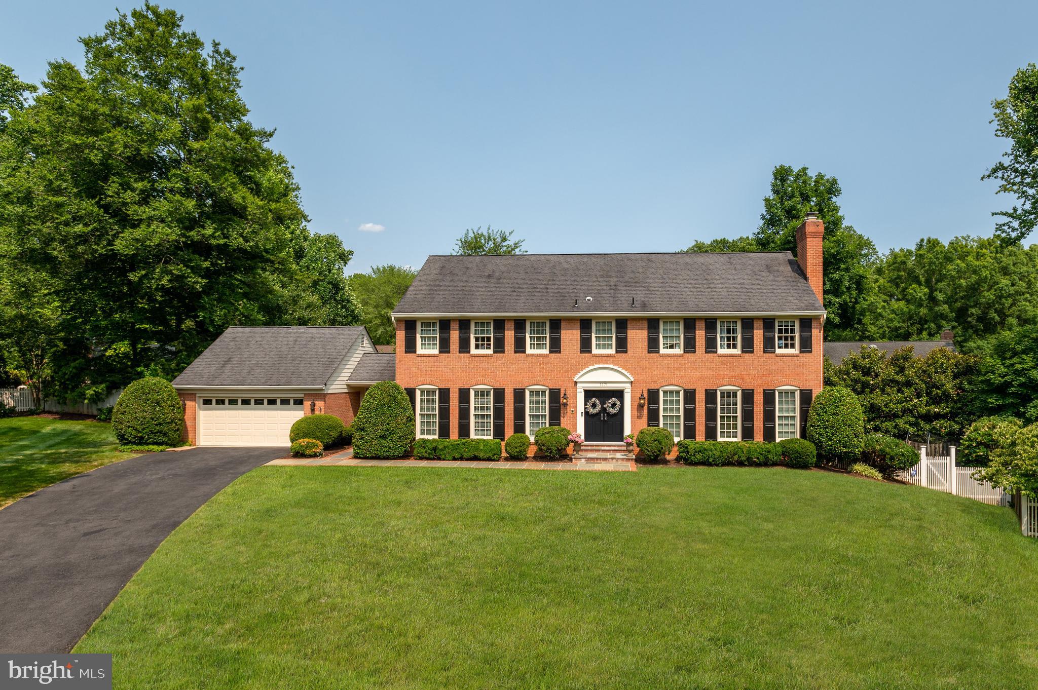 Sited on a private cul-de-sac in McLean’s Timberly neighborhood, 1171 Huntover Court is a 1977 brick Colonial boasting beautiful upgrades and elegant design details across 3 levels and 5,900 total square feet. Nestled on nearly half an acre, the outdoor amenities are as stunning as the home’s interiors. Showcasing a walkout Main Level Deck and Lower-Level Patio, the residence’s outdoor entertaining spaces provide the perfect respite while overlooking the lush greenery and mature trees of the fully fenced rear garden. Offering 5 Bedrooms and 4.5 Bathrooms throughout an open floor plan, the interior living spaces include gleaming hardwood flooring, detailed moldings and wainscotting, and large windows allowing in lots of natural sunlight. 
The front flagstone path surrounded by boxwoods leads you into the entry foyer with new marble floors, which is flanked by the Living Room with fireplace. The Gourmet Kitchen offers direct access to the formal Dining Room with views of the front garden and western sunlight. Upgraded with high-end stainless-steel appliances and boasting 2 sinks and ample counter space, the kitchen opens to the Breakfast Room and the expansive Family Room with built-ins, a fireplace, and direct access to the rear deck and garden, as well as the separate Main Level Office/Den. A conveniently appointed Laundry / Mudroom offers interior access to the attached 2-Car Garage. 
The Upper Level showcases the home’s principal guest quarters to include an expansive Primary Suite. Boasting gleaming hardwood flooring, 2 walk-in closets, a Sitting Room/6th Bedroom and a spa-like Bathroom complete with jetted spa tub, luxury steam/sauna shower and dual vanities, the Primary Suite includes views of the rear garden with eastern sun exposure. Three additional Bedrooms, each providing ample closet storage, and 2 Full Bathrooms are located on the Upper Level. 
The multifunctional, walkout Lower Level features a sprawling Recreation Room and Billiards Room, complete with Wet Bar and Gas Fireplace, that opens to the residence’s spacious Rear Patio for more informal entertaining. An additional Bedroom and Full Bathroom are located on this level as well as a large Storage/Utility Room and walk-in cedar closet.