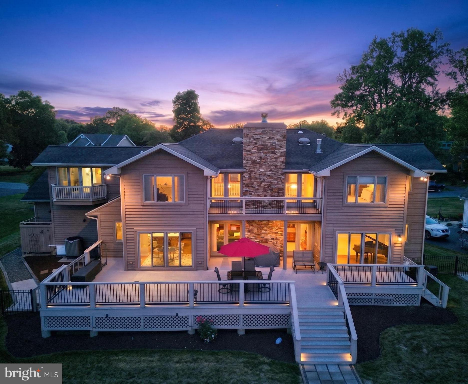 Experience exceptional waterfront living on beautiful Red Mill Pond in this custom-built home built by Garrison Homes, thoughtfully designed to maximize panoramic water views from nearly every room. Situated on an oversized one-third-acre lot with public sewer and its own private dock and boat ramp, this property offers the perfect blend of luxury, comfort, and coastal lifestyle.  Meticulously maintained and extensively updated, this five-bedroom, four bath residence showcases quality craftsmanship throughout. The striking Pennsylvania cherry stone exterior accents are echoed inside by the dramatic floor-to-ceiling two-story wood burning fireplace, creating a warm and timeless focal point. Rich custom cherry cabinetry is featured throughout the home, complementing the gourmet kitchen equipped with a center island, gas cooktop, wall oven, microwave, and an expansive buffet/bar area designed for effortless entertaining.  The flexible floor plan offers room for everyone, including two versatile flex spaces that can serve as home offices, additional bedrooms, hobby rooms, or fitness areas. A private guest suite with its own full bath is located on the second floor, while the luxurious primary suite features breathtaking pond views, sitting room, gas fireplace, jetted soaking tub, and separate stall shower.  Outdoor living is equally impressive, with multiple spaces to relax and enjoy the waterfront setting, including a welcoming front porch and 2nd floor front porch, an expansive rear deck, and rear balcony overlooking the pond.  Recent improvements provide peace of mind and modern efficiency, including a one-year-old roof with new gutters and gutter guards, newer Pella doors on the rear, two high-efficiency hybrid heat pump HVAC systems with gas backup (both just four years old), upgraded appliances, a tankless water heater plus a traditional tank water heater also only 5 years old, a whole-house water treatment system, an encapsulated crawl space, and security system. Built with resilience in mind, the exterior walls are 8" walls and the lower level sits approximately 12 feet above flood elevation.  Three fireplaces—one wood-burning and two gas—add warmth and ambiance throughout the home.  Whether you're boating, fishing, kayaking, or simply enjoying the tranquil waterfront setting, this exceptional property delivers a rare opportunity to live at the beach while enjoying the privacy of your own dock and the convenience of a community boat launch. A truly special waterfront retreat where quality construction, thoughtful updates, and stunning views come together.