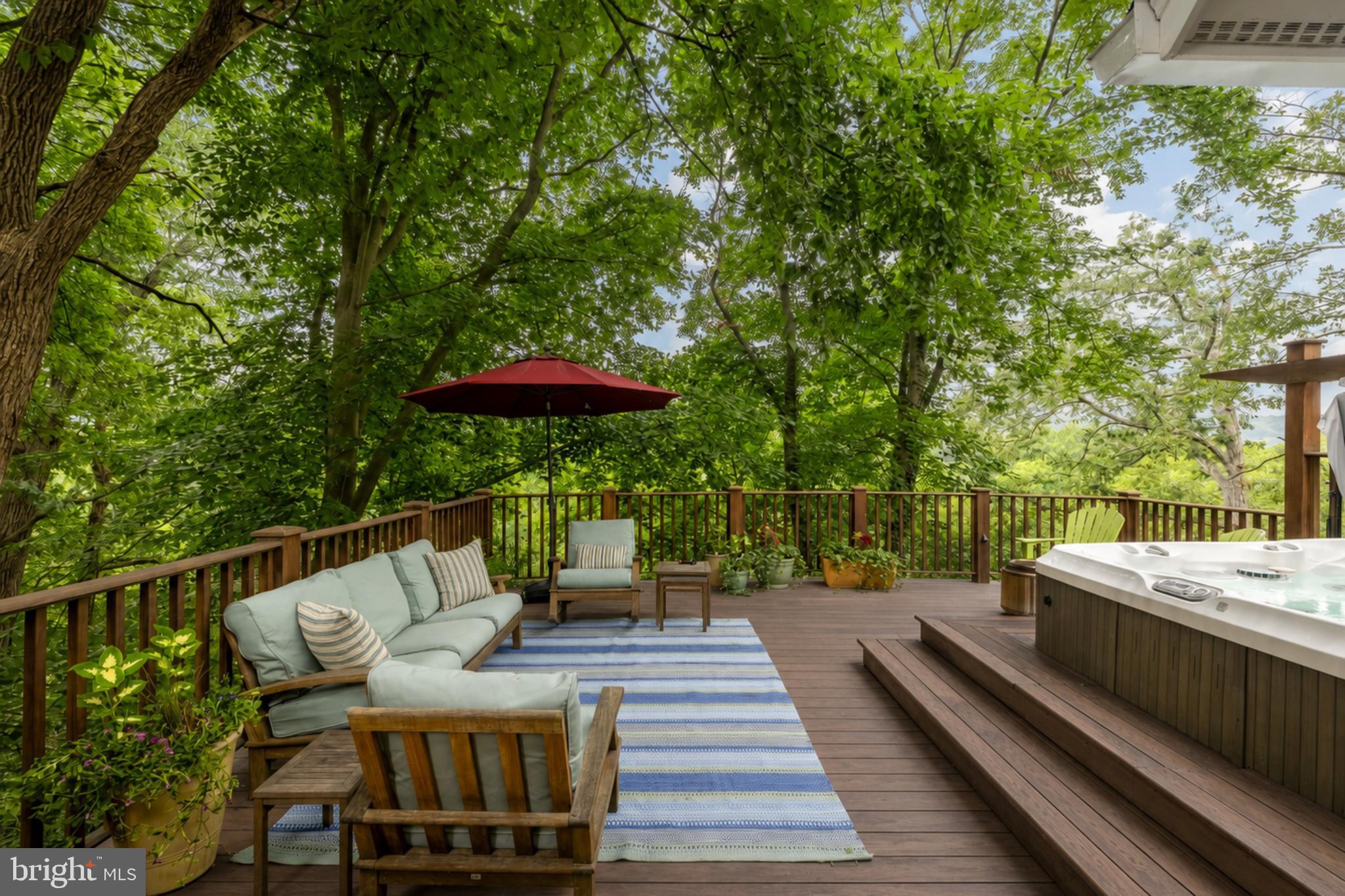 Behind its storybook Craftsman cottage façade, 6512 Ridge Drive unfolds into an expansive, light-filled home offering more than 4,400 square feet across four beautifully finished levels. Set on a quiet dead-end street in Bethesda’s coveted Brookmont neighborhood, this 4 bedroom, 3.5 bath residence combines timeless character, thoughtful updates, and an exceptional connection to the outdoors.

A welcoming foyer opens to the gracious living room, where a striking stone wood-burning fireplace creates a warm focal point. Hardwood floors continue into the formal dining room and through to the heart of the home: a beautifully remodeled kitchen and family room with a gas fireplace, walls of windows, and peaceful sunset views. The kitchen features custom cabinetry, a generous island with built-in storage, stylish backsplash, premium appliances including a six-burner BlueStar Platinum gas range with an oversized oven, and a breakfast nook with built-in seating. The open flow of the main level makes it ideal for both intimate gatherings and large-scale entertaining.

The kitchen opens directly to an extraordinary outdoor retreat. Measuring approximately 25 by 32 feet, the one-of-a-kind Ipe 800 sq. ft. deck was constructed on commercial-grade steel and feels suspended among the trees. When the leaves fall, there are sweeping views of the Virginia Palisades and the C&O Canal. With a covered dining area, multiple seating spaces, a hot tub, and a natural gas stainless grill, the deck offers an exceptional outdoor living experience. Below, a covered patio extends the indoor-outdoor living space, while established gardens in the front attract butterflies and add seasonal color.

Upstairs, the primary suite feels like a private getaway, complete with a renovated en suite bath, walk-in closets, and a balcony overlooking the C&O Canal. The additional bedrooms are generously sized, and all of the home’s bathrooms have been recently remodeled. The top floor provides versatile space for an additional 5th bedroom, office, playroom, art studio, or lounge with rough-in for bathroom.

Filled with natural light, the lower level offers a spacious media and recreation area with room for movie nights, a home gym, or an additional living room. A private bedroom with its own full bath and separate entrance creates an ideal arrangement for guests, an au pair, or multigenerational living. Two laundry areas, one upstairs and one on the lower level, along with two storage sheds, add everyday convenience.

Brookmont offers a distinctive balance of neighborhood charm, natural beauty, and accessibility to DC, which is only half a mile away. Two neighborhood entrances connect directly to the C&O Canal and its miles of walking and biking paths. The Capital Crescent Trail intersects with the top of the neighborhood, and additional internal trails flow from a local arboretum. The village green, a community space that hosts annual events and Brookmont’s own year-round farmers market, is just one block away, and the neighborhood boasts its own playground, basketball court, tennis court and tree swings. Safeway, Wagshal’s, CVS, Praline Bakery and other everyday conveniences are all close by. The home is also located within the highly rated Walt Whitman High School cluster. With its unexpected scale, exceptional outdoor living, and rare connection to both nature and the city, 6512 Ridge Drive offers a Brookmont lifestyle unlike any other.