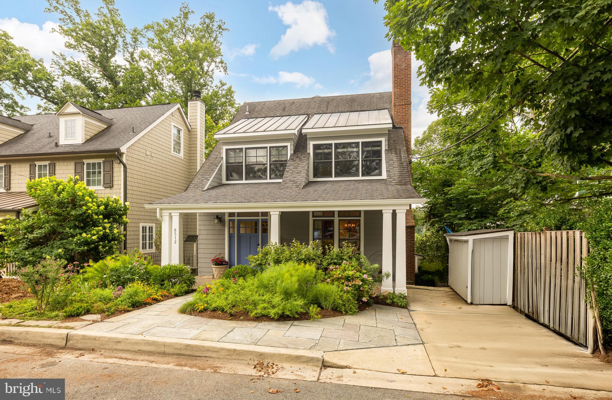 Behind its storybook Craftsman cottage façade, 6512 Ridge Drive unfolds into an expansive, light-filled home offering more than 4,000 square feet across four beautifully finished levels. Set on a quiet dead-end street in Bethesda’s coveted Brookmont neighborhood, this 4 bedroom, 3.5 bath residence combines timeless character, thoughtful updates, and an exceptional connection to the outdoors.

A welcoming foyer opens to the gracious living room, where a striking stone wood-burning fireplace creates a warm focal point. Hardwood floors continue into the formal dining room and through to the heart of the home: a beautifully remodeled kitchen and family room with a gas fireplace, walls of windows, and peaceful sunset views. The kitchen features custom cabinetry, a generous island with built-in storage, stylish backsplash, premium appliances including a six-burner BlueStar Platinum gas range with an oversized oven, and a breakfast nook with built-in seating. The open flow of the main level makes it ideal for both intimate gatherings and large-scale entertaining.

The kitchen opens directly to an extraordinary outdoor retreat. Measuring approximately 25 by 40 feet, the one-of-a-kind Ipe deck was constructed on commercial-grade steel and feels suspended among the trees. When the leaves fall, there are sweeping views of the Virginia Palisades and the C&O Canal. With a covered dining area, multiple seating spaces, a hot tub, and a natural gas stainless grill, the deck offers an exceptional outdoor living experience. Below, a covered patio extends the indoor-outdoor living space, while established gardens in the front attract butterflies and add seasonal color.

Upstairs, the primary suite feels like a private getaway, complete with a renovated en suite bath, walk-in closets, and a balcony overlooking the C&O Canal. The additional bedrooms are generously sized, and all of the home’s bathrooms have been recently remodeled. The top floor provides versatile space for an additional 5th bedroom, office, playroom, art studio, or lounge with rough-in for bathroom.

Filled with natural light, the lower level offers a spacious media and recreation area with room for movie nights, a home gym, or an additional living room. A private bedroom with its own full bath and separate entrance creates an ideal arrangement for guests, an au pair, or multigenerational living. Two laundry areas, one upstairs and one on the lower level, along with two storage sheds, add everyday convenience.

Brookmont offers a distinctive balance of neighborhood charm, natural beauty, and accessibility to DC, which is only half a mile away. Two neighborhood entrances connect directly to the C&O Canal and its miles of walking and biking paths. The Capital Crescent Trail intersects with the top of the neighborhood, and additional internal trails flow from a local arboretum. The village green, a community space that hosts annual events and Brookmont’s own year-round farmers market, is just one block away, and the neighborhood boasts its own playground, basketball court, tennis court and tree swings. Safeway, Wagshal’s, CVS, Praline Bakery and other everyday conveniences are all close by. The home is also located within the highly rated Walt Whitman High School cluster. With its unexpected scale, exceptional outdoor living, and rare connection to both nature and the city, 6512 Ridge Drive offers a Brookmont lifestyle unlike any other.