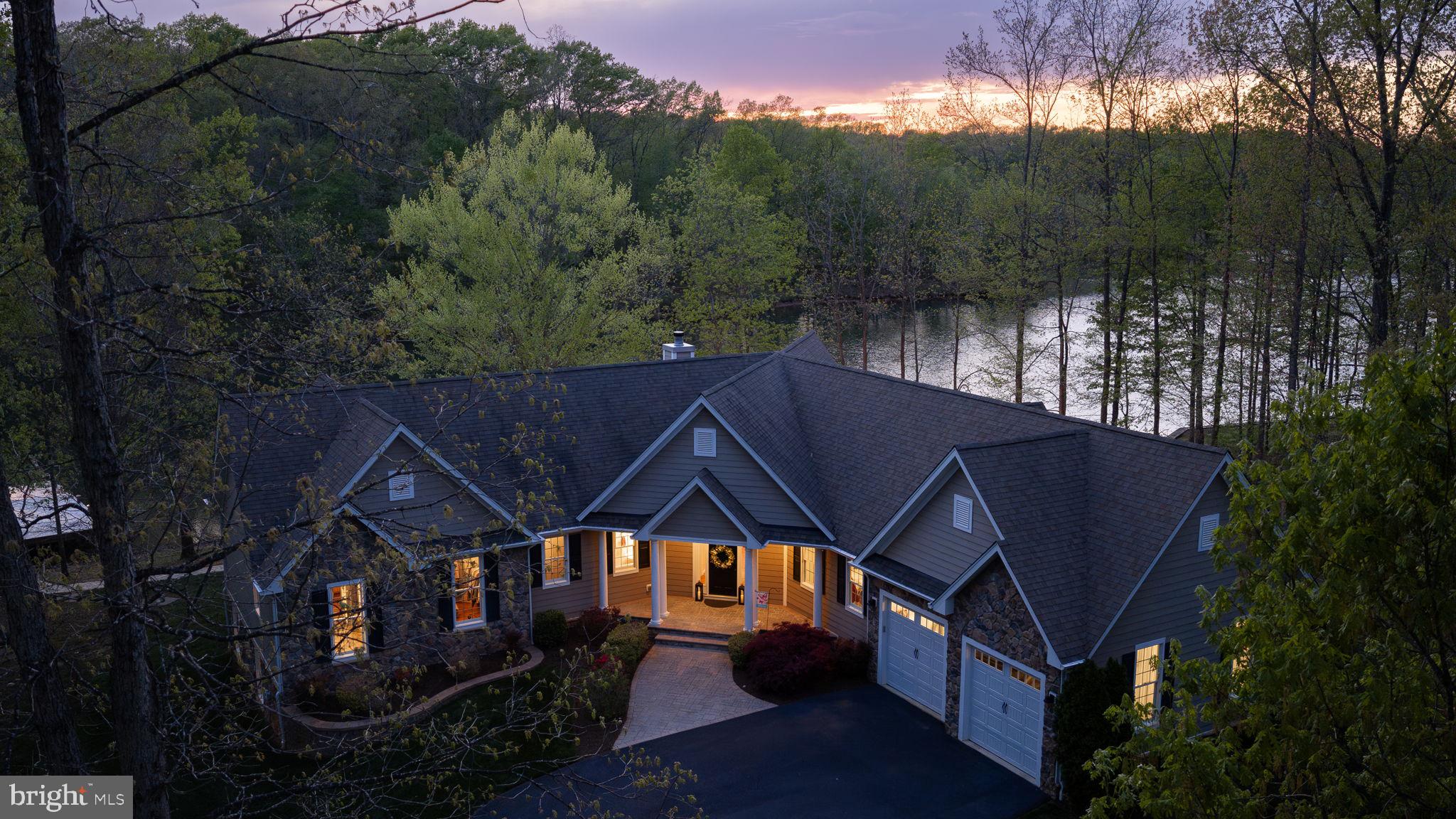 Rental Projection is in MLS Documents Section! Tucked away on the private side of Lake Anna in Noah’s Landing Subdivision, this gorgeous custom-built waterfront home offers the kind of setting that’s hard to find—quiet, private, and right on the water. Set on 1 acre with 230 feet of shoreline and deep water off the boat dock, the property features riprap along the shoreline and a natural, wooded backdrop that enhances the privacy and views. High-speed Firefly fiber internet is available, bringing fast, reliable connectivity to this peaceful lake retreat. Inside, the home is filled with thoughtful upgrades and timeless finishes. The great room showcases vaulted ceilings, expansive floor-to-ceiling windows designed to maximize the lake views, and a wood-burning stone fireplace that anchors the space. Hunter Douglas remote-controlled blinds add both comfort and convenience. The spacious kitchen is built for gathering and everyday use alike, featuring stainless steel appliances, granite counters, a walk-in pantry, center island, soft close cabinets, and a breakfast bar with seating. There is also a stylish wet bar with silestone countertops. Engineered hardwood flooring runs throughout the home, complemented by 9-foot ceilings and a spacious, open layout that creates a bright and connected feel from room to room. The layout offers 5 bedrooms and 3.5 bathrooms—giving the home flexibility for full-time living or extended lake stays. The spacious lakeside main level primary bedroom suite features beautiful views of the lake, his and her walk-in closets, a tiled walk-in shower with two niches, and separate vanities. The lower level offers a welcoming family room, three bedrooms, and two full baths—including one with its own private ensuite for added comfort and privacy. Two of the bedrooms are finished with plantation blinds, adding a clean, coastal-inspired feel that enhances the relaxed lake lifestyle. Outside, the backyard opens up to a massive paver patio with multiple defined areas for seating, dining, and gathering around the fire pit. It’s a natural extension of the home—an easy place to spend the day from morning coffee to evenings under the stars. There is also a dedicated propane line for the grill making grilling out a breeze. From here, a gentle path leads down to the water and boathouse featuring an electric lift, storage room, and a large sun deck that sits right over the deep water. Additional upgrades include a whole-house generator, lake-fed irrigation system, Hardi Plank and stone siding, and a Rinnai tankless water heater. TVs, washer and dryer, garage freezer and extra refrigerator in the storage room convey with the home. With its combination of setting, upgrades, and strong outdoor lifestyle features, this property is equally well suited as a primary home, a short-term rental or a private lake escape. It’s a comfortable, well-equipped Lake Anna home that delivers where it matters most—on the water! Come see for yourself!