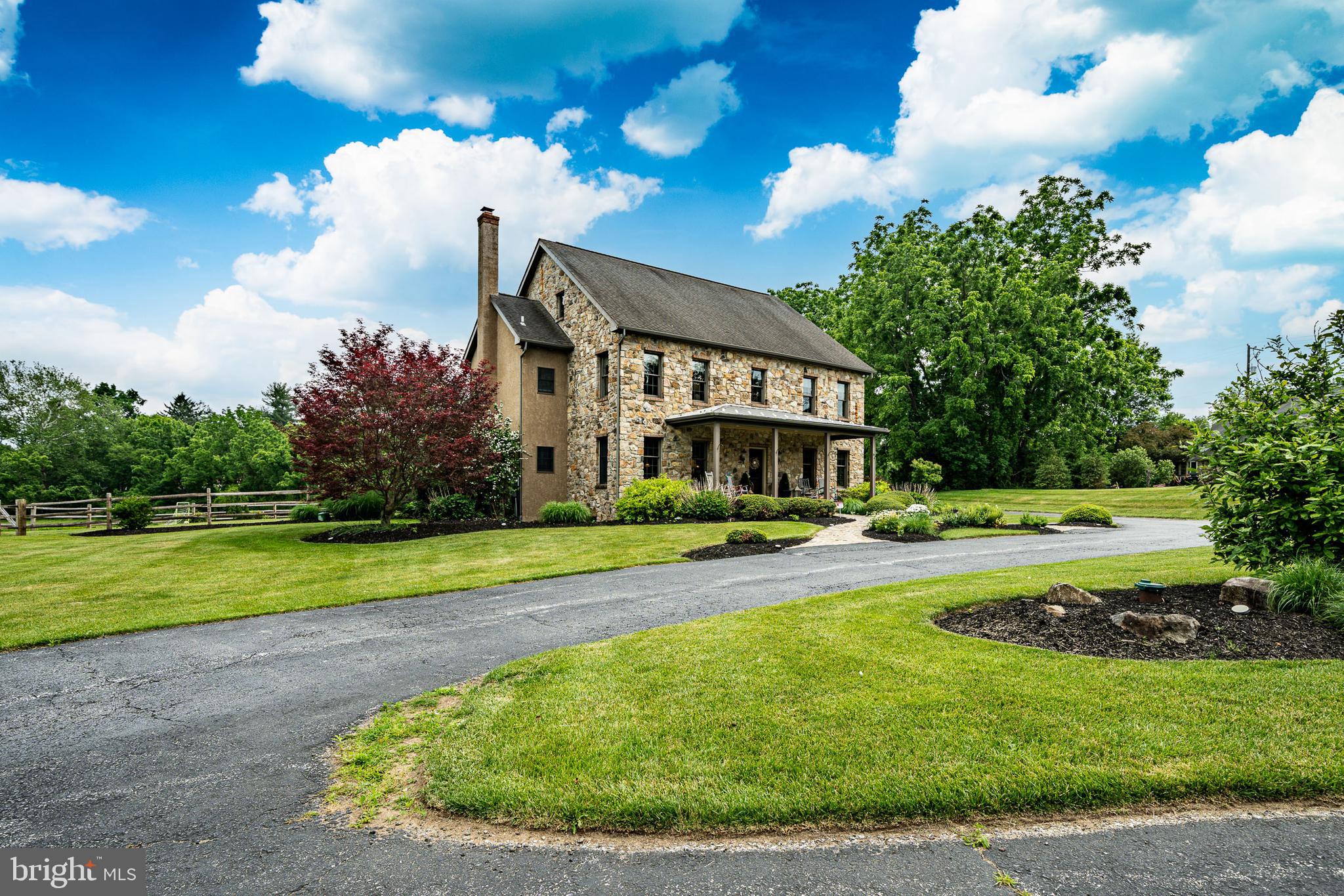 Welcome to this stunning Chester County farmhouse nestled on a breathtaking 5.86-acre setting in the highly sought-after Downingtown Area School District. Combining timeless charm with modern conveniences, this exceptional property offers 4 bedrooms, 3 full baths, 2 powder rooms, a finished walk-out basement, private home office, and oversized 3-car attached garage.

A circular driveway leads to a beautifully illuminated stone walkway and inviting covered front porch with brick flooring. Inside, an open and spacious foyer welcomes you with random-width hardwood floors, abundant natural light, and 9-foot ceilings throughout the main level. Elegant formal living and dining rooms provide the perfect spaces for entertaining, while the impressive family room features a floor-to-ceiling stone wood-burning fireplace, exposed beam ceiling, and custom millwork.

The gourmet kitchen is designed for both everyday living and gathering, featuring custom cabinetry, Corian countertops, a large wood center island, built-in desk area, stainless steel appliances, and a sunny breakfast area with built-in bench seating and storage. Just off the kitchen, enjoy seamless indoor-outdoor living on the covered brick patio complete with electric screens, ceiling fan, and views of the fenced backyard and surrounding countryside.

The second floor offers a luxurious primary suite with custom built-ins, dual walk-in closets, and a spa-inspired bath featuring a Jacuzzi tub, oversized tiled shower, double vanity, and linen storage. Three additional bedrooms, including a Jack-and-Jill suite, provide ample space for family and guests. A remarkable bonus room offers endless possibilities as a home office, recreation room, guest suite, or additional family room and includes a Murphy bed, powder room, multiple closets, and private staircase access.

The finished walk-out lower level expands the living space with new carpeting, recessed lighting, abundant storage, and direct access to the backyard. The third-floor attic is already floored and roughed-in, providing an incredible opportunity for future finished living space.

Additional features include two-zone Lennox propane heat and central air conditioning, a Bradford White hot water heater, first-floor laundry room, storage shed, and extensive storage throughout. Set on nearly six picturesque acres in a prime Chester County location, this exceptional property offers privacy, functionality, and classic farmhouse appeal. A truly rare opportunity and an absolute must-see.