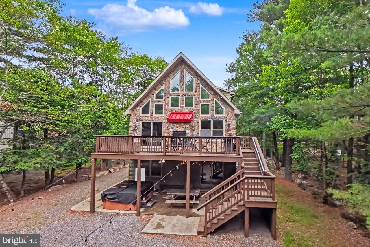 Expansive stone-front Pocono vacation home nestled in popular Lake Harmony Estates with access to it's own private community beach, tennis courts, rare Power boat Lake Harmony, as well as Jack Frost and Big Boulder slopes! This perfect investment property is ideal for guests, boasting 6 bedrooms 3 full baths ( one on each level), central air, an oversized trex deck, and large hot tub, 6-8 car parking, huge firepit for roasting marshmallows, and lush yard with pretty outdoor lighting, ! The sundrenched great room boasts gleaming hardwood floors, dramatic  dual-sided stone fireplace, cathedral vaulted ceilings, stunning wall of windows, nantucket beadboard, chair rail, and a bright slider to the enormous Trex deck . The gourmet kitchen features mesmerizing black granite countertops and peninsula island, and recessed & pendant lighting and opens to the spacious dining area . The open floor plan is perfect for entertaining ! The expansive family room  a game room and media room with knotted pine ceiling,  plush carpeting,  and glistening wood beadboard! There are two bedrooms  on each level have huge closets, plush carpeting, and their own full bathrooms  The ample sized loft can be converted to a 7th bedroom for more earnings!  Plenty to do at the Pocono Raceway, Camelback, Camelbeach, Split Rock's indoor waterpark, Kalahari, Mt Airy Casino, Pocono Premium Outlets, Hickory Run State Park, golfing & whitewater rafting in Jim Thorpe! Approx 100K income. Great turnkey short term rental.