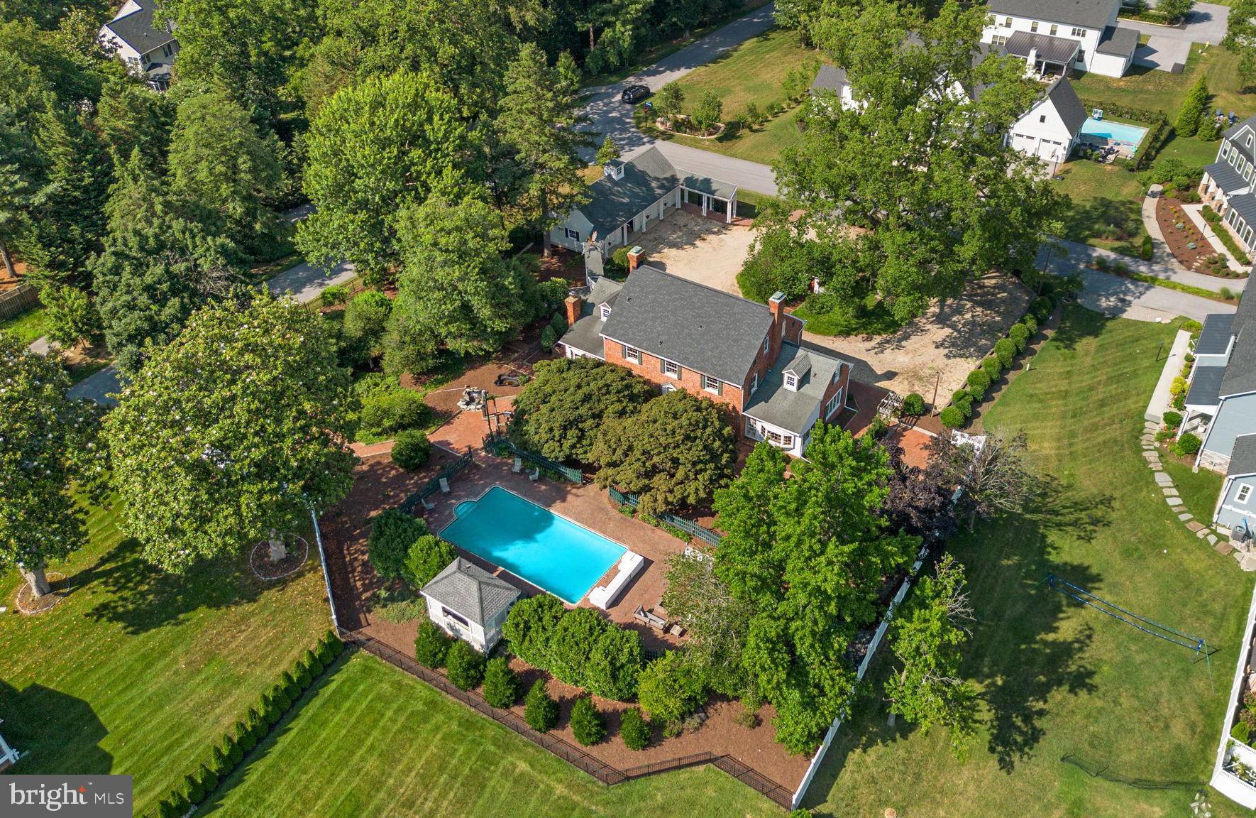 Welcome to a timeless estate where historic charm meets exceptional craftsmanship and modern comfort. Originally built in 1930, this stately all-brick Colonial is surrounded with beautifully landscaped grounds with mature trees, lush gardens, and peaceful green space, creating a truly private retreat.
Rich in architectural detail and character, this remarkable four-level home offers five spacious bedrooms, four and a half baths, and endless flexibility. Original pine hardwood floors, intricate moldings, and custom built-ins are complemented by updates that preserve the home's timeless elegance.
At the heart of the home, the expansive eat-in kitchen is designed for gathering, featuring granite countertops, professional-grade appliances, a charming breakfast area framed by an oversized bow window, and a cozy wood-burning fireplace. Entertain with ease in the elegant formal dining room, complete with exquisite millwork, built-in china cabinets, and an adjoining Butler's pantry. The formal living room showcases a stunning fireplace. The finished walk-up lower level includes a spacious recreation room, full bath, abundant storage, and bar area create the perfect setting for entertaining. With its private layout and full bath, the lower level also offers excellent potential for a sixth bedroom, guest suite, or multigenerational living.
The upper level features three generously sized bedrooms, including a luxurious primary suite with an oversized custom walk-in closet and spa-inspired en-suite bath featuring dual vanities, a soaking tub, separate shower, and convenient laundry. One secondary bedroom currently serves as a home office and includes an adjoining bonus room—ideal for a flexible space. The fourth level provides a private retreat with two additional bedrooms, a full bath, and a spacious sitting room that offers endless possibilities as a media room, game room, or additional lounge space.
Step outside to your own private oasis where an inviting in-ground pool is surrounded by mature landscaping and thoughtfully designed gardens, creating the perfect backdrop for outdoor entertaining or quiet relaxation. Completing the property is an impressive detached four-car garage with abundant attic storage above, providing exceptional space for vehicles, hobbies, and seasonal storage.
From its three distinctive fireplaces and gracious living spaces to its exceptional craftsmanship, flexible floor plan, and unforgettable architectural details, this one-of-a-kind residence offers the rare opportunity to own a home where history, elegance, and everyday livability come together beautifully. Located just moments from Ringgold Cove, this extraordinary property is ready to welcome its next chapter.