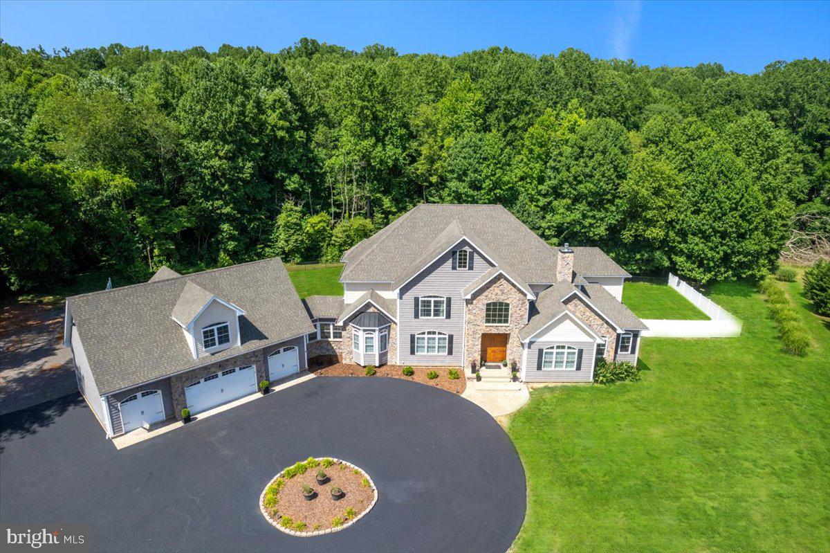 IMPRESSIVE, IMMACULATE, STUNNING ESTATE IN NORTHERN CALVERT COUNTY! This show-stopping residence SHINES with over 10,000 finished square feet upon 10 acres of scenic, private, wooded property.  

Discover a sanctuary of style & sophistication within this incredible home adorned with a spectacular stone front & cedar shake vinyl siding, surrounded by picturesque landscaping. The circular driveway leads to the path of a stamped & stained concrete sidewalk.  You will be greeted by a soaring 8' tall double door entry.  The custom designed front double doors are fiberglass insulated, stained & marine varnished to give a wonderful wood appearance, while maintenance is a breeze!  Indulge in the sheer comfort and elegance of the interior, where 2 x 6 construction & upgraded insulation choices ensure a cozy atmosphere in every room. The main level showcases the ultimate, enormous owner's suite with double door entry to both the primary bedroom and bathroom. 

The culinary enthusiast will delight in the gourmet kitchen, a masterpiece equipped with top-of-the-line KitchenAid appliances, custom designed soft-close cabinets and granite countertops. Don't miss the thoughtfully placed pot filler above the 6-burner cooktop with a griddle on the end!  Admire the elegance of the rounded archways & cathedral ceiling in the kitchen nook, creating a welcoming space to enjoy everyday meals or entertain guests. Entertainment is effortless with the main level custom wet bar area, featuring a wine rack, refrigerator, and under cabinet lighting. Move seamlessly into the grand family room with a two-story stone fireplace, an extraordinary coffered ceiling, and custom millwork columns, offering a perfect setting for family gatherings or cozy evenings by the fire.

Retreat to the luxurious Owner's Bedroom with LED recessed lighting, a tray ceiling, dual ceiling fans, and an en-suite bath adorned with 24x24 tile, dual vanity sink cabinetry, granite countertops.  The deep & oversized soaking tub features designer plumbing fixtures, a removable wand & tiled bath surround. A 5x5 arched fixed picture window above the soaking tub provides lovely wooded views. The owner's shower is tiled to the ceiling with decorative listello tile trim detail, dual shower heads, a removable shower wand, rain shower head, a tiled bench and frameless glass enclosure. Revel in the abundance of storage space with two walk-in closets.  The Owner's suite windows face the private & mature hardwood out back. The sitting area also has a plumbing rough in for a future wet bar! This space is the perfect blend of functionality and elegance. 

Explore the finished basement with 9 ft ceilings.  Enjoy the tranquility of the screened-in porch & maintenance-free composite deck, or host outdoors on the expansive patio. The spacious garage appeals to any car enthusiast with room for 4 cars and additional space for a potential apartment or office above. From the charming plantation shutters & crown moldings to the marvel that is the remarkable rounded staircase, as well as thoughtful details (like the fire suppression system) this home offers a blend of luxury and practicality. Embrace the serene oasis that is 10 acres of privately owned land in Northern Calvert County. This home is located off of a cul-de-sac & set back from the road, complete with a fenced area for added privacy & safety. This home also features premium systems & mechanicals - dual zoned HVAC with gas back up heating, a 500 gal propane tank & a best available technology nitrogen septic system for efficiency. This home is a harmonious blend of modern amenities and timeless elegance. 

Located just minutes away from parks, hiking trails, nature preserves as well as shopping, dining, entertainment and TOP RANKED schools as well as major commuter route 4, the location cannot be beat! 1915 Owensville Court is an elite home and property, well built and designed with the highest level of detail. Schedule your showing today!