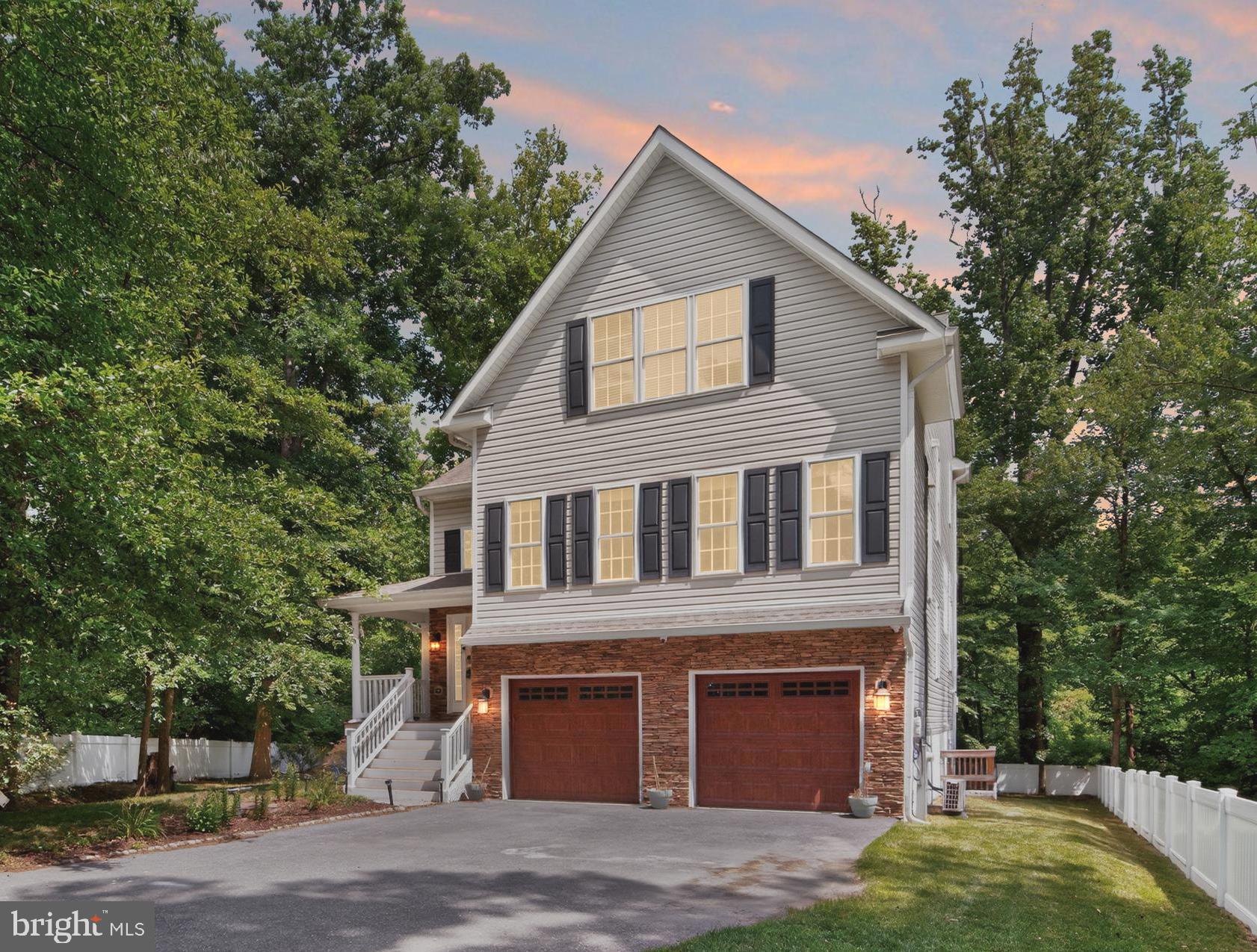 Welcome to this stunning 4-bedrooms, 4-bath single family home built in 2019 and offering over 3,400 square feet of beautifully designed living space, a private wooded backdrop, and exceptional indoor-outdoor living. The light-filled main level showcases an open floor plan with soaring ceilings, rich hardwood flooring, elegant crown molding, and expansive windows that fill the home with natural light. At the heart of the home, the chef's kitchen features crisp white cabinetry, stainless steel appliances with newer Samsung dishwasher and refrigerator, a large center island with seating, and picturesque views of the surrounding trees, creating an inviting space for both everyday living and entertaining. The adjoining family room is ideal for cozy movie nights or cheering on your favorite team, complete with a mounted TV, Bose soundbar, subwoofer, and a warm propane fireplace. Host memorable gatherings in the separate formal dining room with an adjacent living room, offering plenty of space for entertaining. A main-level bedroom and full bathroom provide excellent flexibility for guests or a private home office. Upstairs, the spacious primary suite offers a peaceful retreat with vaulted ceilings, a private upper deck, two generous walk-in closets, and a light-filled en-suite bath featuring a separate luxury shower, soaking tub, and double vanity. Two additional bedrooms share a full bathroom with a dual-sink vanity and a tub/shower combo. A convenient upper-level laundry room adds ease to everyday living. The finished lower level with a seperate exterior entrance, large rec room, full bathroom, and two unfinished storage closets offers additional living space to entertain, create guest quarters, in-law suite or kid’s play area. One of the home’s most impressive features is the outdoor space. Enjoy two incredible decks overlooking the wooded area, a charming front porch, plus a fully fenced yard for outdoor enjoyment, entertaining, or simply relaxing in a private natural setting while roasting marshmallows on the firepit. Parking is effortless with an attached two-car garage featuring durable epoxy flooring, a Rivian EV charger, an extended driveway accommodating four or more vehicles, and an additional paved parking pad. Thoughtfully equipped with today's smart home technology, this home includes electric smart blinds with remote controls, Nest smart thermostats and sensors, Lockly smart locks, a camera security system, and 6 wall-mounted LED TVs that convey! Ideally located for both work and play, commuting is a breeze with convenient access to I-95 and I-295, close proximity to Fort Meade, and just a 10-minute drive to BWI Airport. Enjoy endless shopping, dining, and entertainment at nearby Arundel Mills and Live! Casino. This exceptional home truly has it all. Don’t miss this!