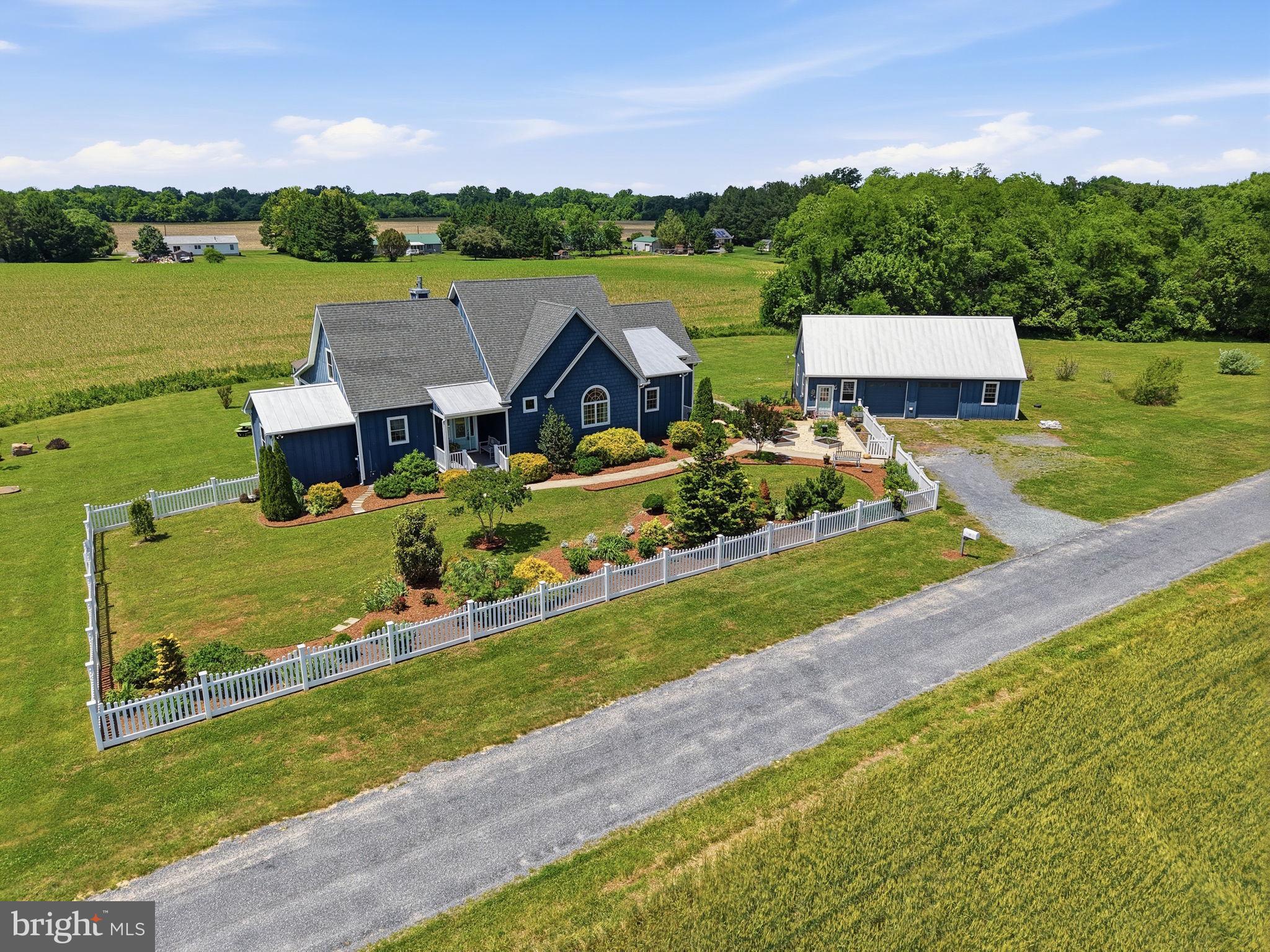 Thoughtfully designed and built in 2017, this private retreat sits on nearly 7 peaceful acres just 5 minutes north of historic Chestertown and 30 minutes from Middletown, Delaware. Surrounded by farmland and mature landscaping, the property offers the perfect balance of modern comfort, flexibility, and quiet Eastern Shore living. The heart of the home is the stunning chef’s kitchen featuring cathedral ceilings, top-of-the-line appliances, a large center island, and separate pantry. The kitchen flows into the family room with a propane fireplace and French doors leading to the rear screened porch where you can take in views of the yard and surrounding countryside. The main level primary suite offers a spacious bathroom and oversized dressing room closet. A second main level bedroom provides access to a full bathroom and dedicated office. An additional bonus room on the main level offers flexibility for dining, hobbies, crafts, or running a business from home. Upstairs, you’ll find two additional bedrooms and a full bathroom. The partially finished walkout basement expands the living space even further with a full bathroom and flexible recreation or guest area with direct access to the backyard. Additional features include an oversized detached two-car garage with attic storage above, numerous garden beds throughout the property, and a peaceful setting that offers privacy, space, and room to truly enjoy the outdoors.