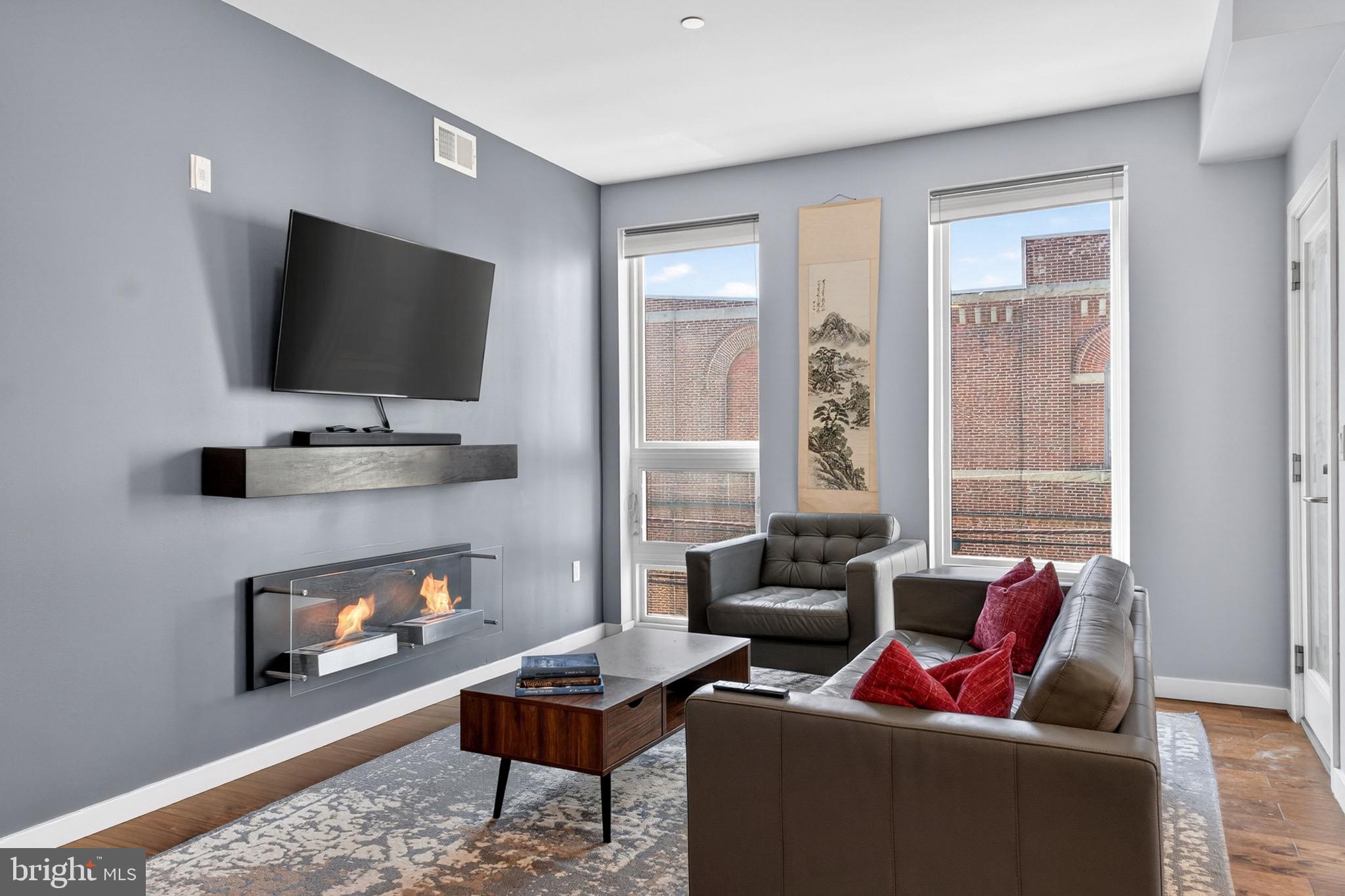 **Qualified buyers may be eligible for a temporary 1% one-year interest rate buy down. Contact listing agent who will put connect you with one of our preferred lenders for details and full disclosures.** Welcome to Unit 201 at The OTTO! With its south-facing exposure and nearly floor-to-ceiling windows, the space stays bright and inviting from morning through late afternoon, naturally drawing you into the main living area.
Just off the entry, the home opens up into a seamless kitchen, living, and dining space that’s easy to settle into. The oversized island with waterfall countertops becomes the natural gathering point—whether it’s a quiet morning coffee or a full evening with friends. This unit has been upgraded with a sleek ethanol fireplace, giving the space a subtle focal point and a bit of extra warmth and character, especially as the sun starts to set.
Tucked just beyond, the primary suite feels private and calm, with two closets and a well-designed en-suite bath featuring a double vanity, glass-enclosed shower with bench seating, and soft natural light from its southern exposure. A second full bathroom, laundry closet with storage, and the convenience of being just steps from the elevator round out the layout.
Upstairs, the building’s green roof deck offers a different perspective—open sky, city views, and space to grill or unwind.
Set in the heart of Brewerytown, you’re a short walk to Fairmount Park and just minutes from Girard Avenue, Kelly Drive, and I-76, making both commuting and weekend plans easy.
A deeded parking space is included with the sale, and the remaining tax abatement adds meaningful value. Schedule your showing today!