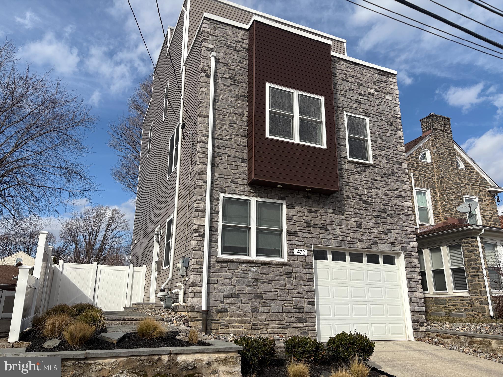 A house so cool…. other houses wish they could be just like it.  But they can’t because this one is in a class of its own.  Welcome to 472 Cinnaminson Street; built in 2017 with careful craftsmanship and an eye toward style.   Situated within easy walking distance to the Ivy Ridge commuter train, a playground, the Gorgas Lane trailhead to Wissahickon Park, shopping and restaurants, this well-established neighborhood feels like small town while the startlingly big and fully fenced back yard gives suburbs!   After taking in the beautiful exterior with its Ledge Stone frontage, wood accent bay and EP Henry paver walkway, you’ll enter into the Main Level foyer to find an immaculate, modern interior designed for today’s lifestyle.  Oak hardwood floors grace this and all of the upper levels. The foyer offers a secure steel front door with Mission-style stained glass, access to the one car garage and a coat closet with California Closet system.   There are two bedrooms on this level, both currently used as home offices.  The back bedroom is the larger of the two and features a walk in California Closet plus sliders to the EP Henry patio and expansive back yard... a rare find in this neighborhood with approximately 2000 sq feet of  private back lawn.  The hall bath, with its quartz accents and oversized shower, offers direct access to this bedroom as well as to the foyer hallway.   The 2nd Level is one large open space with light-filled windows on every wall.   There is the Dining Area with coffered ceiling which blends into the central kitchen featuring an 8 foot island and built-in butler pantry with granite countertops.   Soft-close, solid wood Shaker cabinets provide ample space for storing all your kitchen needs.   Stainless steel appliances include gas range with griddle burner, brand-new GE Profile refrigerator, an undermount kitchen sink with disposal, dishwasher and gooseneck faucet and a built-in microwave.  A large Living Room area completes this level.   The 3rd Level is home to the Primary Suite with walk-in California Closet and ensuite bath.   The Primary Bath features a barn door, double sink with granite countertop and oversized shower.   The 4th Bedroom is also on this level and faces the front of the house, featuring its own private balcony and California Closet.    A hall bath with tub/shower plus the laundry closet complete this level.   Get a bird’s eye view and a great suntan on the roof deck where you’ll not only get a city skyline view, but will also get to see fireworks from every angle!  The roof deck is ready to rock with Sonos speaker wiring.   But wait, there’s more!   The fully carpeted basement provides a large recreation or family room plus storage and utility areas.   Home has dual heating and cooling zones, 9’ ceilings and 2 years remain on tax abatement.  Buyers will receive a one year HSA home warranty at the time of settlement.