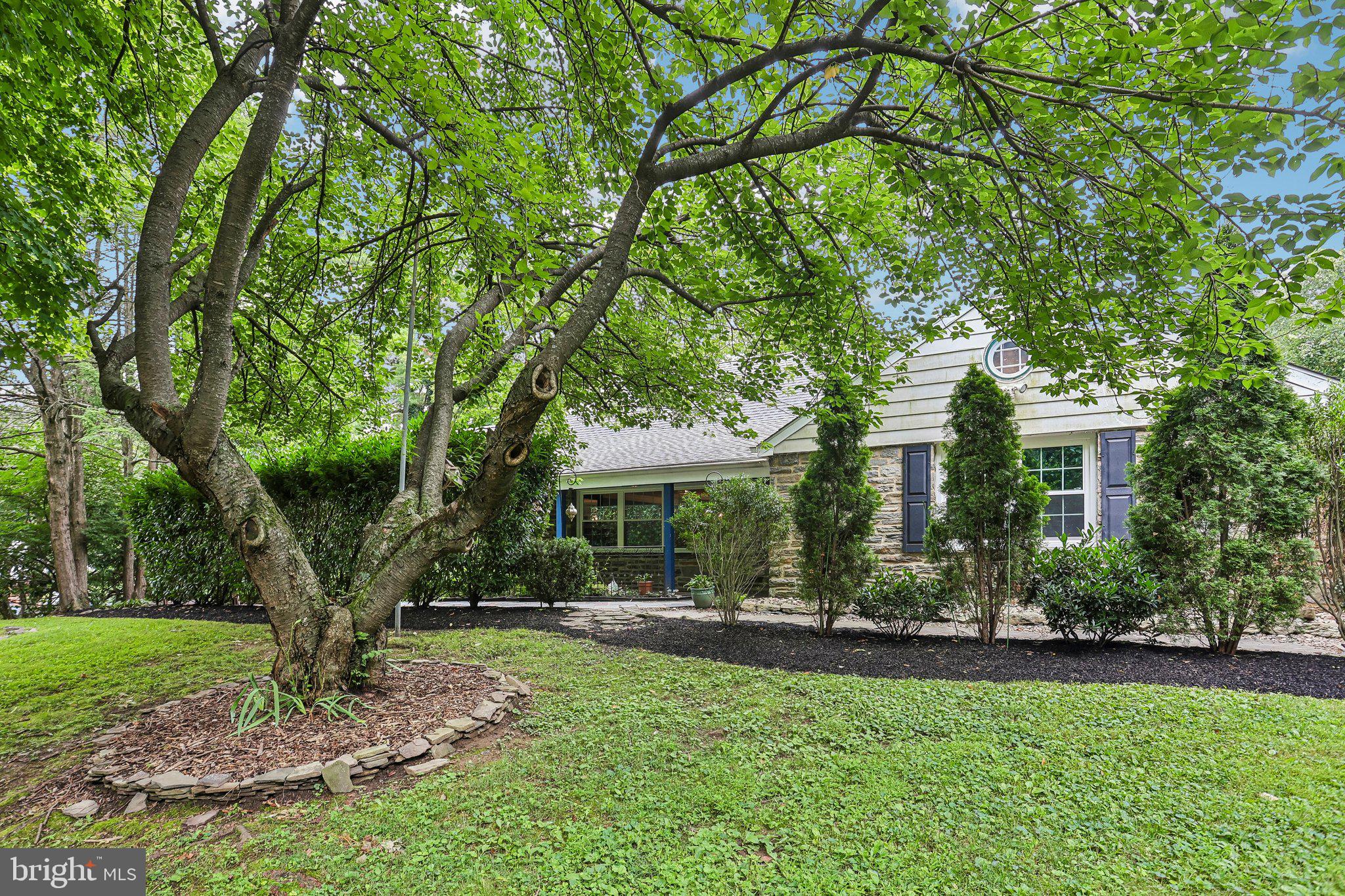 Bring your vision and unlock the potential of this sun-drenched expanded Cape, offering a sprawling, nearly 2800 square foot flexible floor plan with 4-5 bedrooms and the convenience of first-floor living. Priced accordingly and ready for your updates, this spacious home presents a wonderful opportunity to create something truly special. A welcoming foyer opens to an expansive living room highlighted by a stone fireplace and abundant natural light. The generously sized dining room provides plenty of space for entertaining and accommodating all your furnishings. Located just off the dining room, the kitchen enjoys easy access to the enclosed atrium, creating a seamless extension of the living space and the perfect setting for  indoor/outdoor dining and entertaining. The first-floor master bedroom suite features a private full bath, ample closet space, and its own entrance to the atrium. Two additional first-floor rooms offer exceptional versatility—one as a bedroom and the other ideal for a nursery, study, home office, hobby room, or potential fifth bedroom. Hardwood floors are believed to exist beneath the carpeting on the first floor. Finally, an exceptionally large utility/laundry/mud room provides substantial storage and offers convenient access to the rear yard. Upstairs, you'll find two spacious bedrooms and a full bath, creating the perfect set-up for guests, extended family, or private living quarters.
Constructed with timeless Pennsylvania bluestone and low-maintenance vinyl siding, the home also features an oversized attached two-car garage. Outside, mature trees and established landscaping create a peaceful, private setting enhanced by a vegetable garden, and a slate patio. A large shed with electric service provides additional storage, workshop space, or room for hobbies. Conveniently located in Wyncote near shopping, dining, public transportation and commuter routes with easy access to Center City, this home offers incredible space, flexibility, and endless possibilities for its next owner. Don’t miss your chance to make this special property yours!