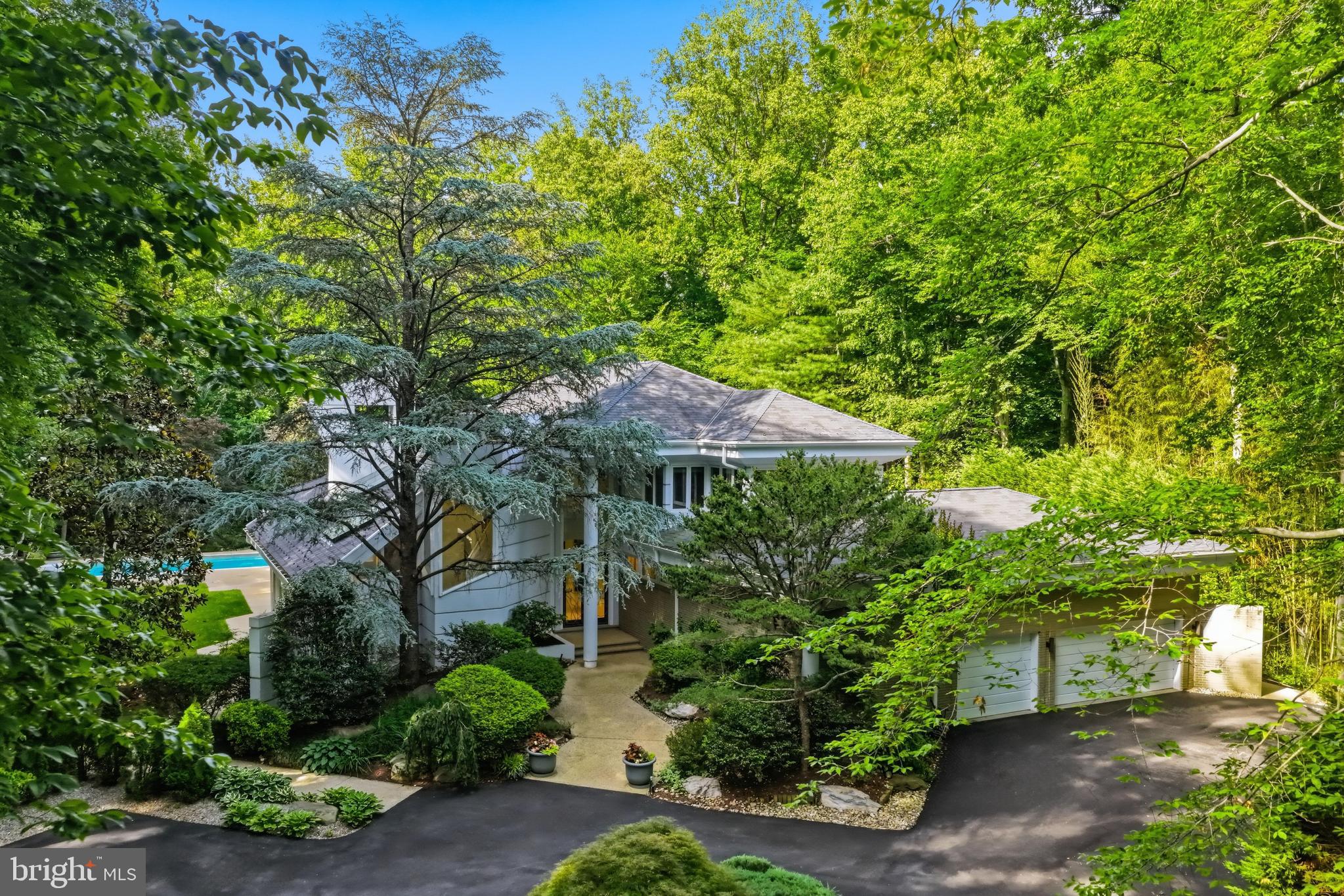 Spectacular does not begin to describe this fabulous residence! Tucked away at the end of a quiet cul-de-sac behind private gates, 9 Oaklyn Court is one of the most striking contemporary residences to come to the market in Potomac this year. Perfectly sited on 2.24 private, level acres with mature landscaping and a resort-style pool, the property offers a serene, parklike setting with exceptional outdoor space and a true sense of seclusion. Designed to impress, the home is filled with natural light, soaring interiors, and captivating views from almost every room. 
A dramatic two-story covered entry introduces expansive living spaces defined by 20+- foot vaulted ceilings, walls of glass, and skylights that flood the home with light. The main level is thoughtfully designed for both grand-scale entertaining and everyday living, with a seamless indoor-outdoor flow. The impressive, step-down living and family rooms are separated by a two-sided gas fireplace, and walls with steps for displaying artwork. The family room has a built-in bar. Each light-filled room has sliding glass doors to the back yard and swimming pool. 
Even the most discerning cook will appreciate the beautiful, renovated kitchen with top-of-the-line appliances, dramatic cabinetry, a center island, built-in buffet, circular designer-glass eating space with stool, and an adjacent eating area that overlooks one of the two large patios, perfect for outdoor eating and barbecuing. Off the kitchen is the dining room with special lighting and floor-to-ceiling windows overlooking the side yard. 
The main level also features the spacious primary suite, a delightful retreat with access to the pool and grounds. The bedroom has a custom wall of built-ins with cabinets, lighted niches, and room for a TV. The adjacent study could also be used as a sitting room, and there are two well-designed large walk-in closets. Two full bathrooms include three separate vanities, a step-up tub, and step-up stall shower. Completing this level are a handsome, cherry-paneled library, two powder rooms, and a large laundry room.
The upper level features four bedrooms, two with en-suite bathrooms and a third full bathroom. The balcony overlook offers an impressive view of the stunning main level.
The light-filled lower level provides a variety of options for informal gatherings. A huge recreation room, lounge with bar area, exercise room, hot tub room and separate bathroom, an additional bedroom with en-suite bathroom, and plenty of storage space complete the interior of this fabulous, approximately 9,900-square-foot house.
The grounds are equally impressive, with a gated, lighted long driveway; beautiful post lanterns; heated pool; expansive patios; and beautifully fenced grounds with room for a future tennis or pickleball court. Ideally located adjacent to Avenel, without the restrictions of an HOA, this exceptional offering combines architectural presence, privacy, and convenience in one of Potomac’s most desirable settings.
