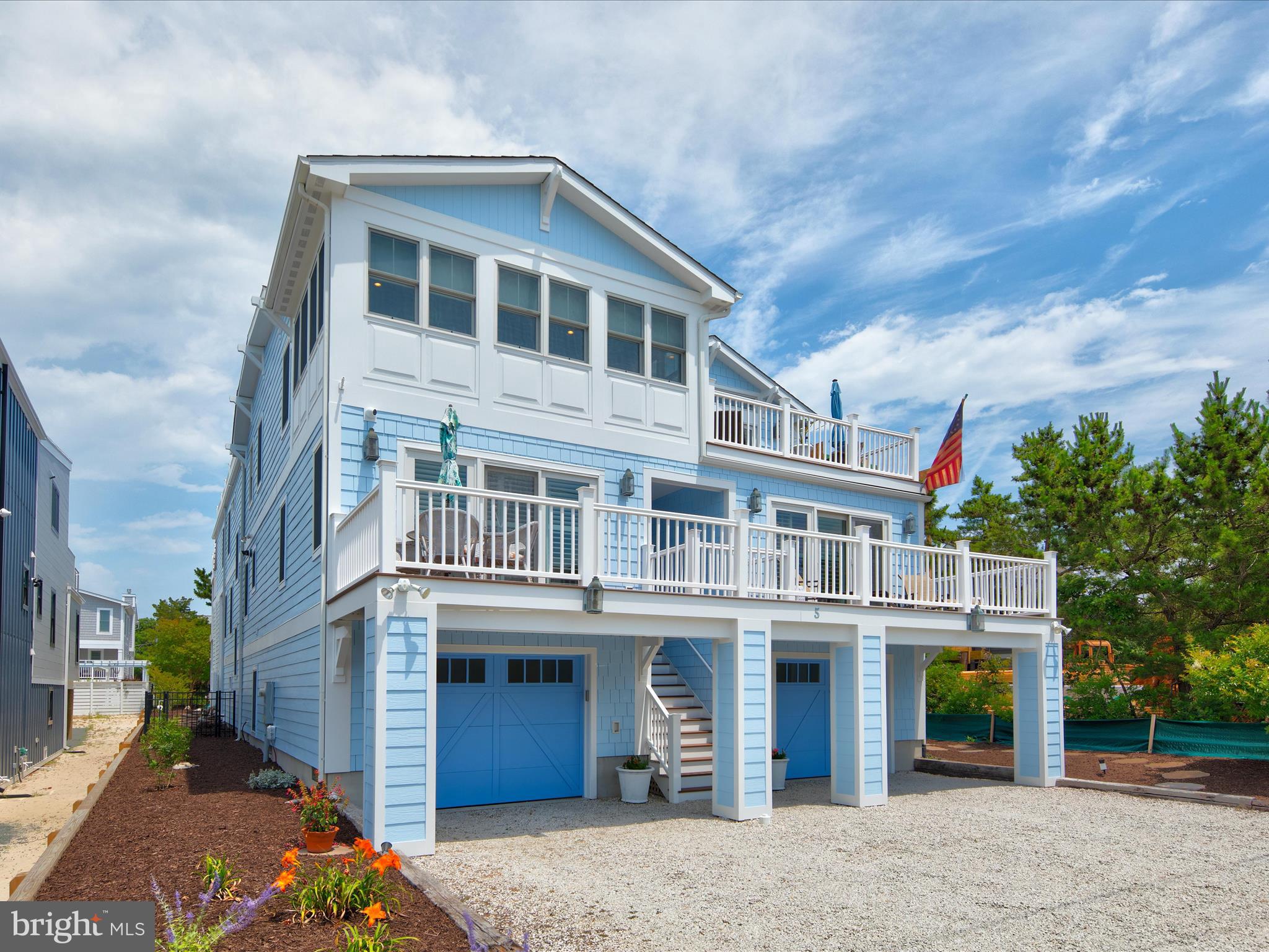 Built with an upscale design aesthetic and quality sensibilities, this coastal styled home checks all of the boxes that a discerning buyer could ask for. With plenty of space to make this your home or home away from home, this thoughtful design provides low maintenance finishes and multiple spaces for extraordinary living, dining and entertainment.
 
Multiple decks invite outdoor living  including a private balcony off of the primary bedroom, a deck off of the living and bar lounge, a second level deck with access to the dining room, and a waterside entertainer’s deck with gas service for outdoor grilling.  The decking extends to a gracious winding stair that rises up to a spectacular roof top deck.  Outdoor living and entertaining venues are endless and include a ground level walk-out paver patio enclosed with private breeze flow walls on two sides, two showers, and a fenced rear yard.
 
Inside, an elevator services three levels, each with gracious elevator halls clad in ship-lap wainscoting that continues into a winding stair. The main entry level is host to a very welcoming living space equipped with a wet bar, taps, fridge and full-sized ice maker perfect for beginning any festive occasion.  The primary bedroom suite, also on the main level, is sided by a private balcony and two walk-in closets outfitted with wardrobe organizer systems in each.  A relaxing spa-like bath follows, replete with an inviting soaking tub, and a walk-in shower offering three body sprays, rain shower and hand shower, each with a separate valve control handle. Two additional en-suite bedrooms, laundry center, elevator hall and open stair complete the main level.
 
While the open plan design enhances views and traffic flow, the architectural ceiling detailing elegantly defines the spaces from above, and the floor plan incorporates a gas fireplace sided by open glass shelving that separates the great room and dining room.  Adjacent to both rooms, a well-appointed chef’s kitchen offers furniture-grade custom cabinetry, a contrast center island with turned legs, professional appliances including a full-sized ice maker, wine cooler, and gorgeous Taj Mahal quartzite countertops that wrap the entire kitchen and peninsula breakfast bar. Tucked in behind the kitchen is a delightful coffee bar with a dedicated sink and a spacious walk-in pantry.
 
Light from waterside windows stream into the open hall reaching the entries to the office, a fourth en-suite bedroom, and a fifth bedroom that is furnished with built-in shelving adding flexibility to enjoy a library or sitting room. Curated with a timeless coastal aesthetic, this home is richly composed of indoor and outdoor spaces that can accommodate family time, vacation time, as well as gatherings large and small. Come home to inspired living at the beach!