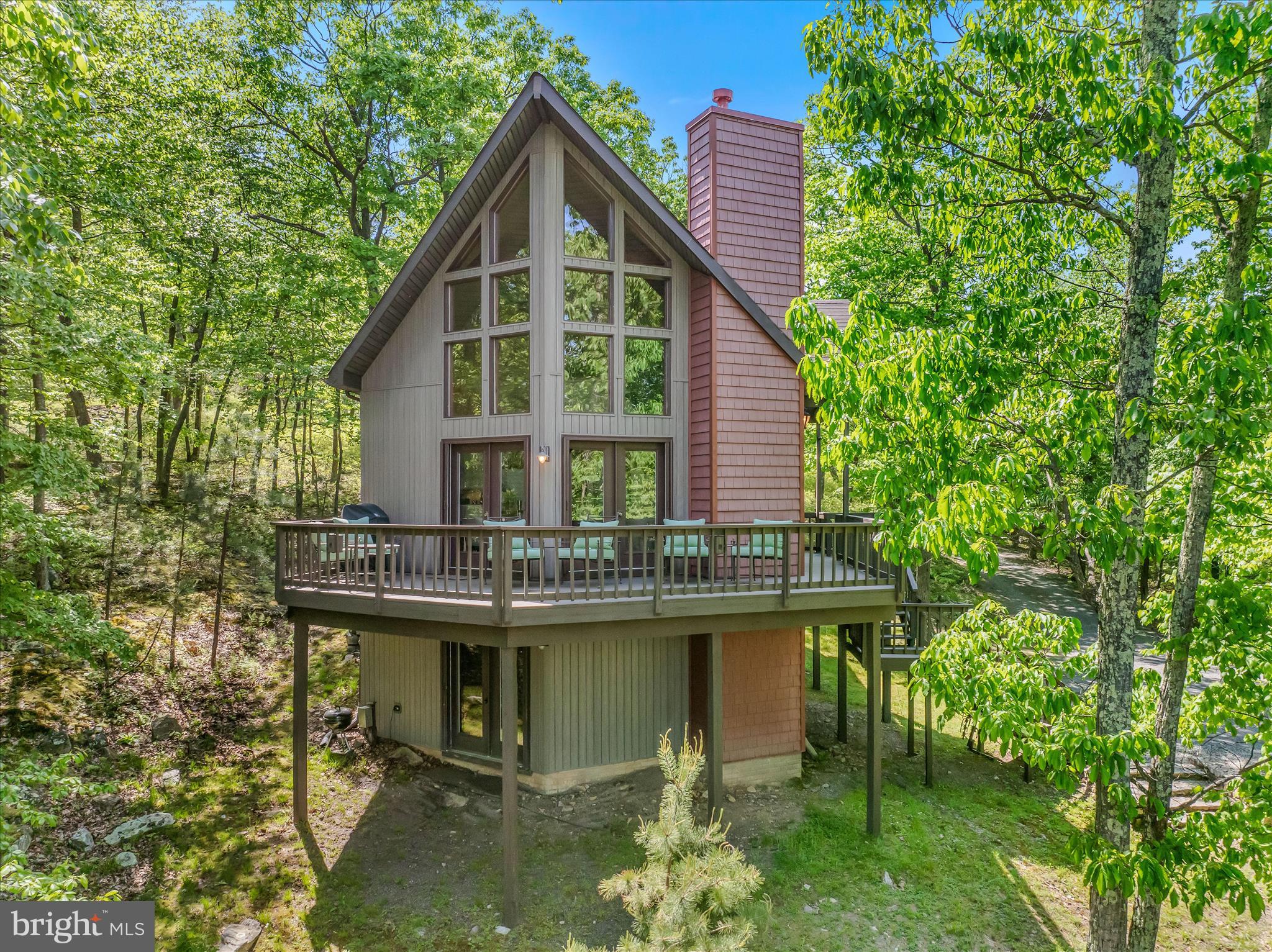 Absolutely stunning mountain top retreat! No detail has been overlooked in this 5-bedroom, 3-bath chalet, nestled on 10 secluded acres within a gated community high atop Cacapon Mountain. At 2,150 feet elevation, you'll enjoy views for miles from the open living area boasting floor to ceiling windows and a cozy gas fireplace. The main level also features a kitchen with a Viking range and Subzero refrigerator, an office and two guest bedrooms opening onto a shady screened in porch. Upstairs, the luxurious primary suite features its own screened sleeping porch, creating a peaceful sanctuary immersed in nature.  The lower level offers two additional guest bedrooms along with a large family room doubling as a theater and game room. Outside you can enjoy the evening around the firepit or walk directly from the property onto the 6000+ adjoining acres of Cacapon State Park. An adjacent 10-acre lot is also for sale which offers more privacy knowing you are at the end of the road.  AWD/4WD is a must! The road is maintained but steep.  Call your agent today to schedule an appointment to see this magnificent home!