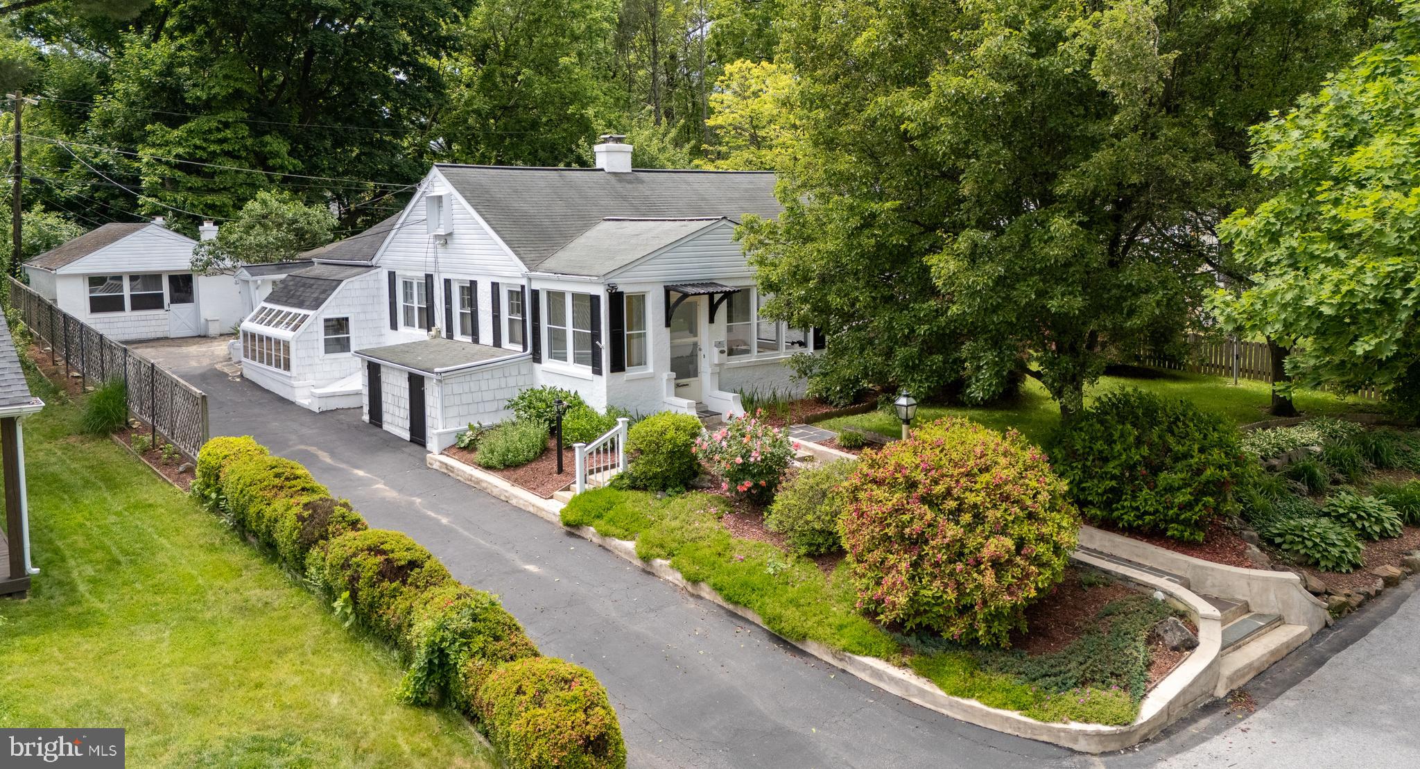 Welcome to 14 Beryl Road, a well-built three-bedroom, two-bath home in a prime Paoli location within the award-winning Great Valley School District, offering a flexible and functional floor plan with unique architectural character throughout. This home was lovingly maintained and expanded over the years, featuring a distinctive architectural flair. A three-season front porch sets a welcoming entry and leads into the formal living and dining rooms highlighted by handsome exposed beams and custom woodwork. The kitchen sits at the center of the home with excellent cabinet storage and counter space, a stainless steel refrigerator and oven, and opens directly to the dining room for easy everyday living and entertaining. Just off the kitchen, a family room connects to a tiled sunroom overlooking the rear grounds AND a large workshop/home office area. Custom woodwork and exposed beams continue throughout these connected living areas, adding warmth and character. From the kitchen, another doorway leads to a versatile finished space with a separate entrance to the side driveway, plus a covered, fully enclosed breezeway with exposed beams that extends to the rear party area. Three bedrooms are served by two full bathrooms with amazing custom tile work. A main-floor laundry area includes washer/dryer hookups and built-in cabinetry for added convenience and storage. The finished lower level features a wood-burning fireplace with floor-to-ceiling stacked brick, a stacked stone bar area, and generous finished living space. This level is paired with a large unfinished workshop and storage area with direct access to the side yard. The outdoor entertaining area sits privately at the rear of the property, overlooking the grassy yard and providing an ideal setting for family gatherings, parties, outdoor grilling, and relaxation. An attached greenhouse with its own exterior entry is perfect for gardening enthusiasts. A deep one-car garage provides excellent additional storage. Lovingly maintained by the same family for decades, this home offers solid construction, thoughtful spaces, and multiple options for living, working, and entertaining, all in a highly convenient Chester County location close to downtown Paoli, parks, trails, and local amenities. A rare opportunity in a sought-after setting—ready for its next chapter. Welcome home!