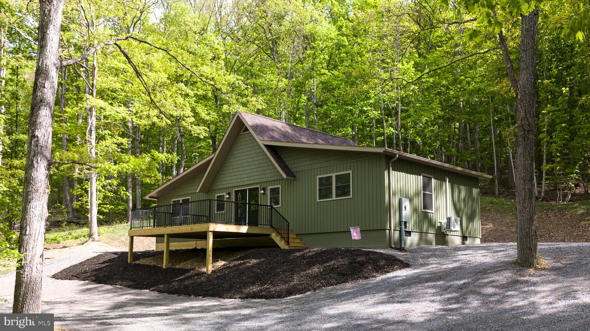 Stunning modern chalet in a private mountain lake community! This once rustic cabin has been completely transformed into a one-of-a-kind mountain/lake retreat, thoughtfully renovated with quality craftsmanship and materials—everything updated except the original framing. Tucked away in a hidden lake community in the WV hills, the home sits on a generous 5.62-acre parcel surrounded by towering hardwoods, offering exceptional privacy and natural beauty. Inside, you’ll find a show-stopping custom kitchen featuring quartz countertops, a large island, and brand-new stainless steel appliances. The open interior is highlighted by soaring vaulted ceilings with tongue-and-groove pine, creating a warm yet modern aesthetic. The enormous primary suite includes a walk-in closet and a beautifully finished bath with a custom tiled shower. The main bath also features a custom tiled shower along with a convenient utility area with washer and dryer. A versatile loft area provides additional space for a bedroom, office, or cozy sitting area. Step outside to a massive deck overlooking a fire-pit area—perfect for entertaining or relaxing under the stars. Perched on a hillside among towering oaks, the home is just a short distance from the community lake and beach, offering easy access to swimming, kayaking, and lakeside enjoyment. A rare opportunity to own a fully re-imagined mountain retreat that blends modern design with peaceful lake community living.