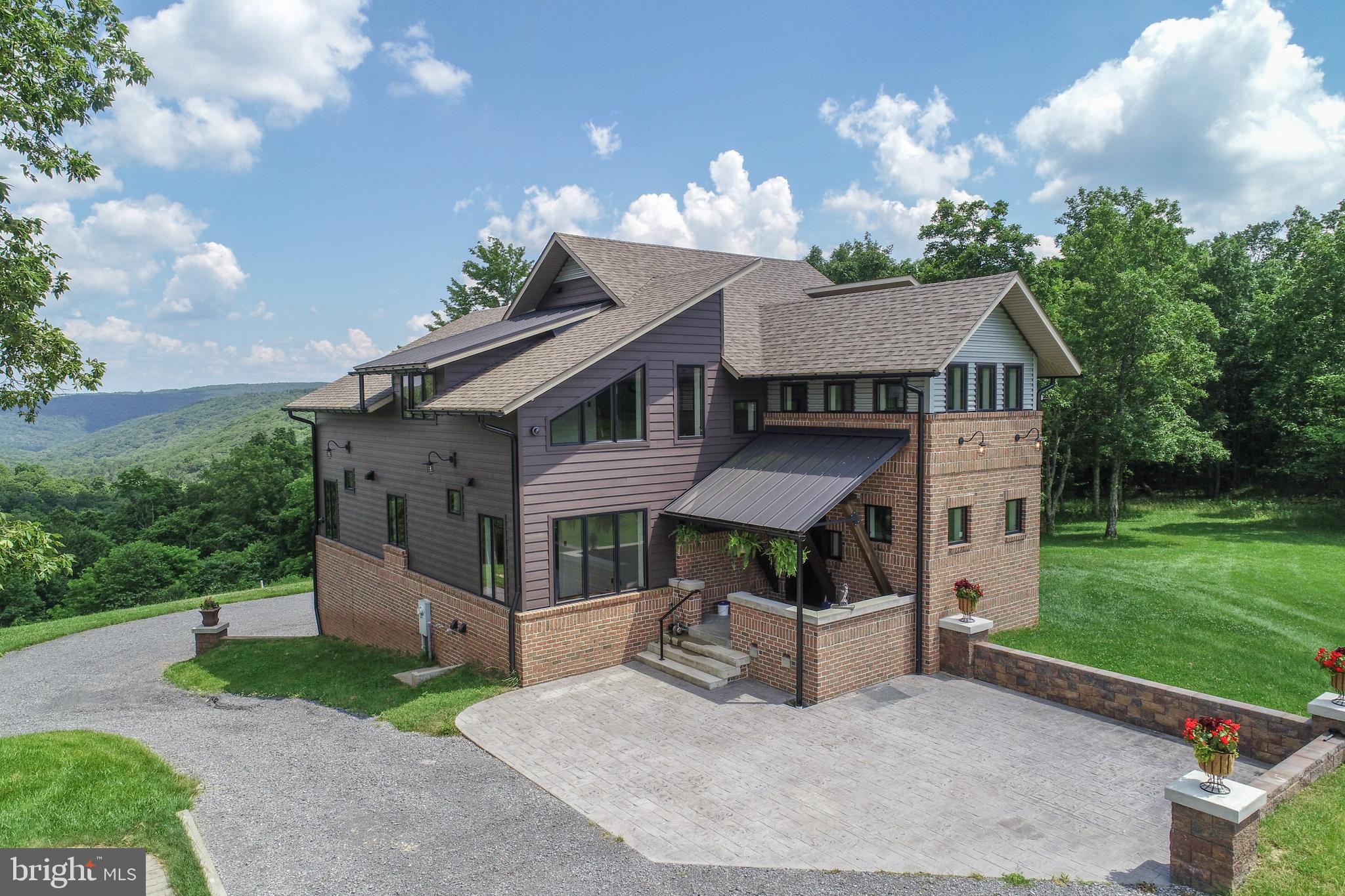 One of Garrett County's most unique and breathtaking mountain estates, this completely custom masterpiece was designed and built with exceptional craftsmanship and attention to detail. The 6000 +/- sq ft custom newly built home is located in the beautiful mountains of Garrett County, Maryland and offers the new owner one-of-a-kind unobstructed panoramic views, serenity, privacy and endless possibilities.  Bordering the Potomac State Forest, up to 64 +/- acres ( 2 parcels, 1  of 50 acres and the other 13.74 acres)of pristine land, offering unmatched privacy, mature woodlands, spacious fields with a stocked pond and natural streams on the property, where the new owner can relax and recharge from everyday life.   The property has also been perc tested for 1 additional residence.  Outdoor amenities include three outbuildings.  There are two finished outbuildings including a quaint accessory dwelling unit featuring a small kitchenette, living space, full bathroom and private deck.  The second finished outbuilding is set up as a bunk house with a covered porch, barn doors and a custom stamped concrete patio with fire pit.  You can use the unfinished outbuilding to store your ATV or UTV.   The hot tub area offers stunning canyon views high above Laurel Run.  This beautiful home has antique oversized brick, Everlast horizontal lap siding, architectural shingles, standing seam metal accents, black Anderson doors and Anderson windows, black half round gutters and downspouts, large exterior decks with custom railing and stamped concrete patios.  This well constructed home features 2x10 exterior walls with spray foam insulation for low heating and cooling costs, radiant in floor heat along with forced air heat and central air conditioning.  The interior walls are covered in native field stone from the property, shiplap siding, drywall, and barnboard.  Added features include handcrafted wormy oak doors and wormy oak flooring and tile flooring.  The interior of this 4 bedroom/5 bath features a luxurious main-level primary suite with walk-in shower, freestanding bathtub and walk-in closet, 1 spare bedroom/office on the main level, 1 main level full bathroom with walk-in shower, main level laundry room with utility sink, 2 upper level en-suites with walk-in shower and freestanding bathtubs, the lower level features a full bathroom with walk-in shower, there are 2 stone fireplaces, gourmet kitchen with extra-large island, walk-in pantry with custom cabinetry and prep sink, dining room, 3 family rooms and three finished utility rooms.  The expansive lower-level family room opens to not one, but two attached finished garages with radiant floor heating for ultimate convenience.  In the interior, you will also find large timbers, metal ceilings and exposed spiral ductwork.  This mountain ranch estate is an outdoor enthusiast’s year-round dream property that offers unforgettable summer gatherings, spectacular fall vista views, a winter wonderland and breathtaking springtime hikes along cascading snowmelt waterfalls.  In addition to opportunities for agriculture and farming, the property includes various trails suitable for nature walks, horseback riding, hiking, biking, ATV/UTV use, cross-country skiing, and snowmobiling.  This large tract of land offers a natural habitat for wildlife that you can admire up close.  The property also offers excellent birdwatching, hunting, fishing and nearby ORV trails.  Located minutes from Deep Creek Lake, MD and Blackwater Falls, WV there are plenty of recreational activities, shopping, restaurants and medical facilities nearby.  A rare blend of rustic elegance, seclusion, and natural beauty—this is truly a once-in-a-lifetime legacy property that you can call home.  Potential for owner financing available.