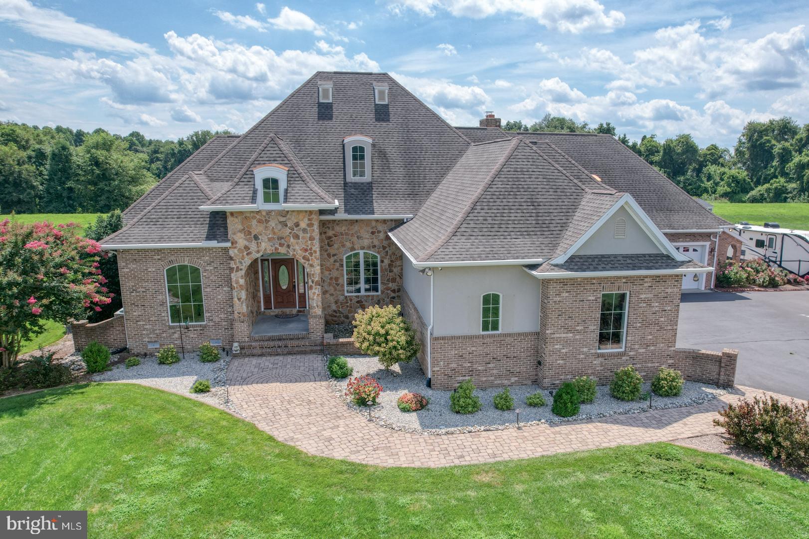 Rare opportunity to assume a 2.375% interest rate - inquire with Listing Agent today! Custom-built 3BR, 3 Full BA, 2 Half BA stone-front  home in a quiet, upscale neighborhood. The grand foyer opens to a light-filled, open floor plan with spacious formal dining, a cozy family room, and a front-facing office with nearly floor-to-ceiling windows. The gourmet kitchen features custom Bertch soft-close cabinetry, granite countertops, oversized island with prep sink and wine cooler, GE stainless appliances, 6-burner propane stove with griddle, pot filler, built-in oven, convection oven/microwave, warming drawer, heated food box, and pantry with built-in organizer.

The sunlit living room offers surround sound, floor-to-ceiling stone fireplace (propane/wood), and multiple windows for abundant natural light. The first-floor owner’s suite includes tray lighting, two custom walk-in closets with built-ins, oversized tile shower with rain head, whirlpool tub, dual vanities, and a private bedroom retreat. A second main-level bedroom includes its own full bath, plus there are two half baths on the main floor. Upstairs, find a spacious bonus room with full bath.

Enjoy year-round comfort in the 8x20 enclosed rear porch. The home boasts two heated/cooled attached garages with space for three vehicles, a concrete pad with 50-amp RV hookup, underground irrigation, programmable sprinkler system, outdoor custom lighting, and wrought iron fenced backyard with double gate access.

Exterior features include a built-in grill island with fridge, patio, fire pit hookup, fountain garden hookup, and professional hardscaping. Utility highlights: encapsulated crawl space with dehumidifier, tankless hot water heater, reverse osmosis, water softener, central vacuum (with kitchen kick-toe), and full security system with cameras, DVR, and ADT monitoring.

Truly one-of-a-kind—schedule your private tour today!