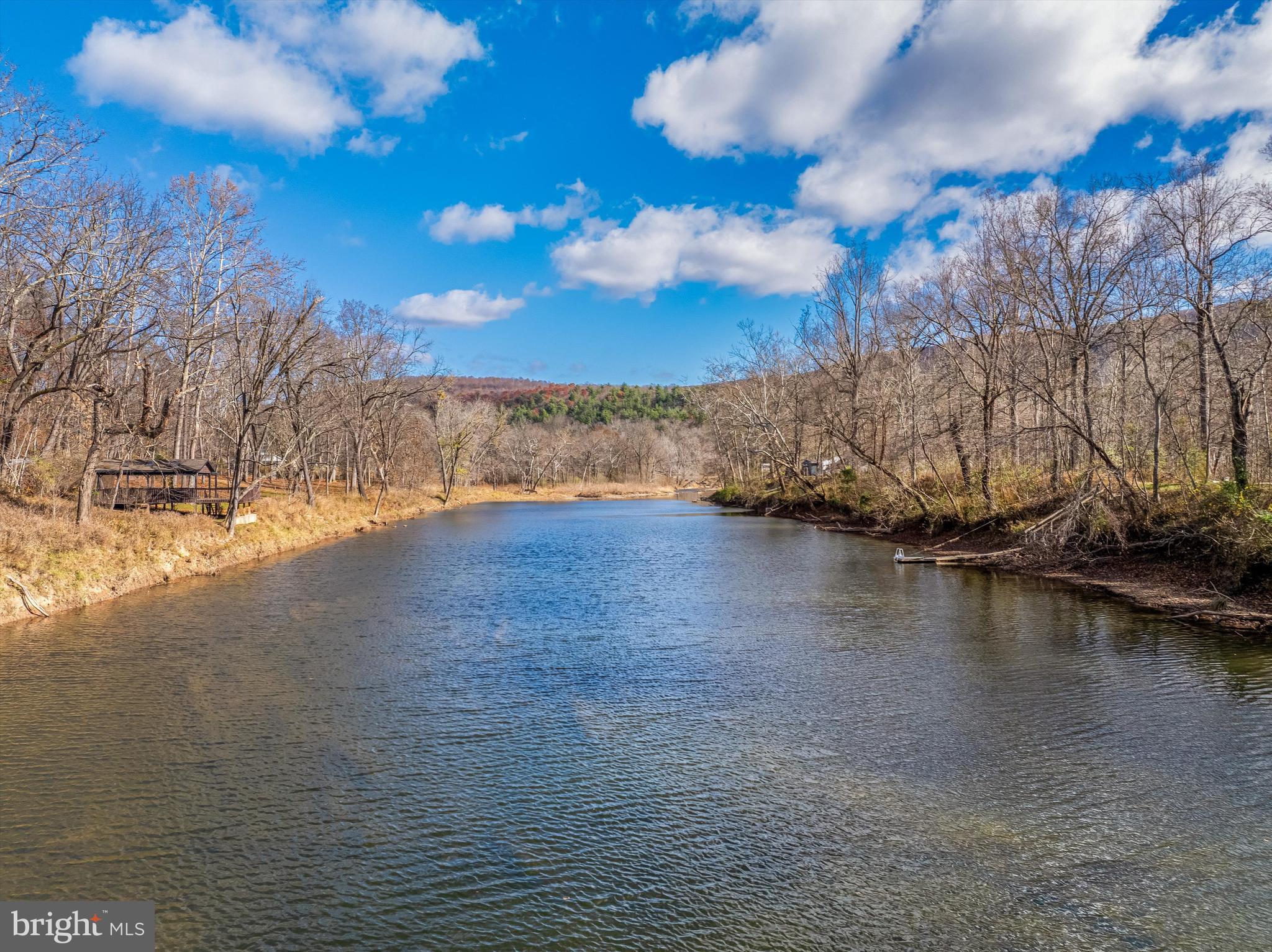 Unwind on 3 acres of picturesque land facing the magnificent Cacapon River.  Engage in camping, fishing, swimming, and kayaking.  Property has carport to park your camper under.  Utilize a well, electricity, and a storage building. Soak up the beauty of the water from your dock and take a revitalizing dip. Prepare meals or unwind by the campfire.  (owner will consider conveying the camper with an acceptable offer)