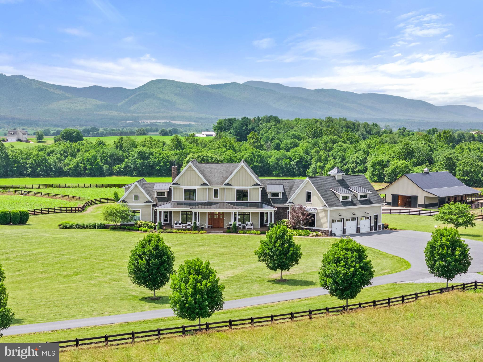 An extraordinary estate with endless possibilities—a refined country home, entertainer’s dream, multi-generational retreat, equestrian haven, or hobby farm. Perfectly sited on 35 acres, this custom Craftsman captures dramatic Blue Ridge Mountain views from nearly every room.
Inviting yet undeniably impressive, the home features hickory wood floors, a floor-to-ceiling stone fireplace, tall wainscoting, and soaring two-story windows that overlook the pool, pastures, and mountains. The chef’s kitchen, with premium finishes and two oversized islands, flows to the dining and great room. The main-level primary suite is large with an indulgent bathroom and custom closet.
Upstairs, two bedrooms share a Jack-and-Jill bath, and a third is ensuite. A large bonus room leads to the second laundry room and gym with rubber sports flooring. In 2022, the lower level was enhanced with a kitchenette, creating a bright, versatile space with 9-foot ceilings, walk-out glass doors, an ensuite bedroom, and a living room with gas fireplace—ideal for guests or extended family.
Outdoors is equally exceptional. A saltwater pool, hot tub, outdoor kitchen, and screened porch with double-sided fireplace are surrounded by stunning hardscape and low-maintenance gardens.
Once a small dairy, now an equestrian’s dream, the 2022-built six-stall barn has a conditioned tack room with half bath, wash stall, and feed room. The arena and round pen, added in 2023, have fiber footing. Eight fenced pastures are ideal for grazing, while larger fields are in crop. Between the house and barn are a playset, in-ground trampoline, chicken coop, and greenhouse.
A massive 48x80 metal barn is perfect for farm use, hobbies, or business. One side is finished, insulated, and radiant-heated; the other side provides flexible storage.
For those who want it all—peace and privacy, luxury and functionality, mountain air and metro accessibility—this property delivers. Located in McGaheysville, home to Massanutten Resort and endless outdoor adventures, with Harrisonburg and James Madison University 20 minutes away, Charlottesville about an hour, and Washington, D.C., just two. A destination, retreat, and legacy property in one—designed to inspire, welcome, and endure.
