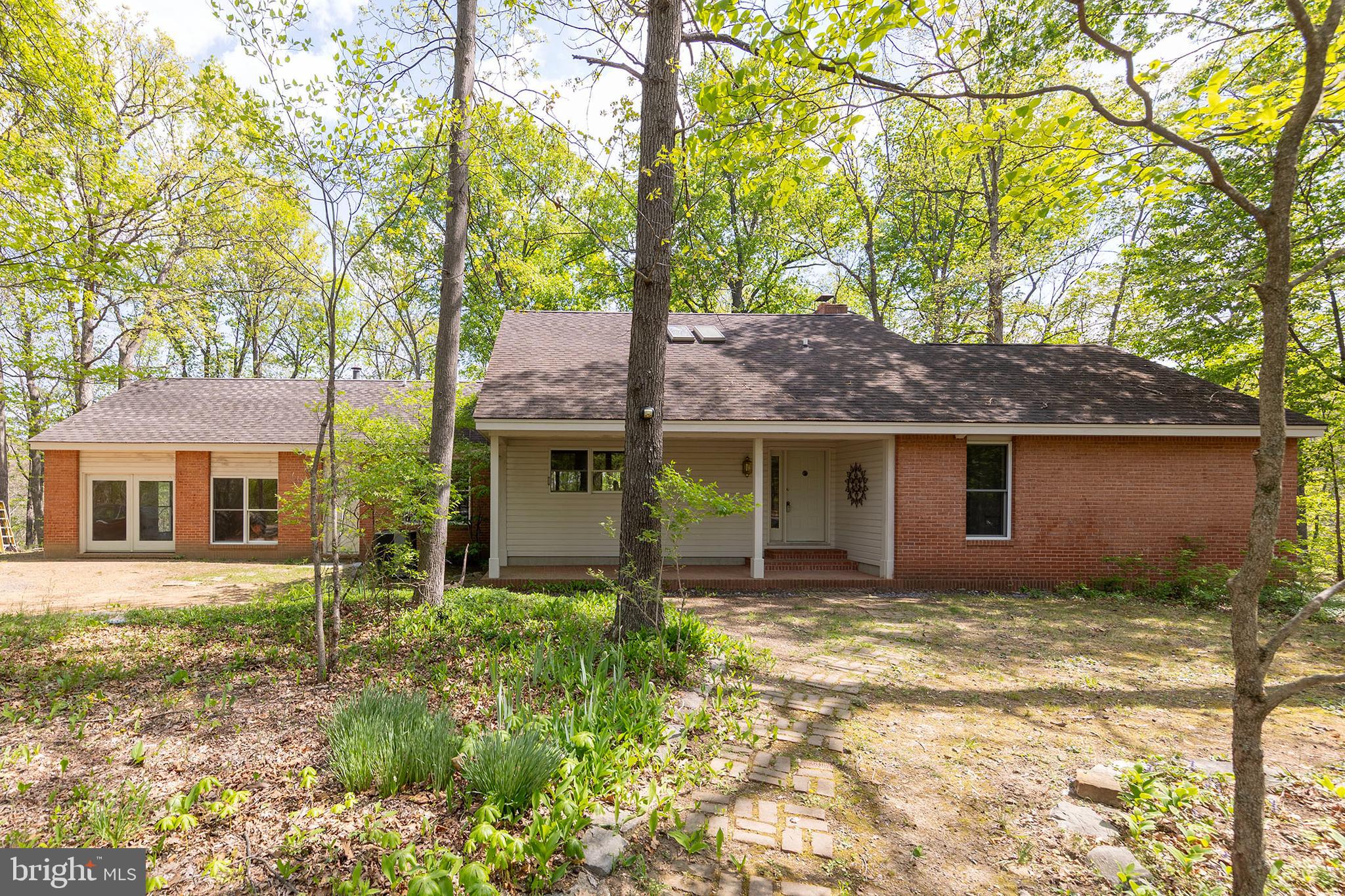 Spacious custom contemporary home set on 8.89 scenic acres, offering peaceful rural living just minutes from Winchester with convenient access to commuter routes. Designed and built by the original owner/architect, this property features 9+ ft ceilings with exposed wood beams, blending character and craftsmanship throughout.

This 4-bedroom, 3-bath brick home offers wood and tile flooring throughout, a cozy living room with a wood-burning fireplace and forced air insert, and a spacious kitchen with ceramic tile countertops and ample workspace. The main level includes a primary suite with a jetted tub and separate shower, along with a guest bedroom for added convenience.

Enjoy the outdoors from the covered front and rear porches or relax on the brick patio overlooking the surrounding acreage. Additional features include two water heaters, an owned 500-gallon underground propane tank, and septic pumped in 2025. High-speed internet is available.

Seller is in the process of dividing the land and establishing an easement—see attached plat for details. Seller will also replace roof with acceptable offer. Septic system is designed for <#BR.