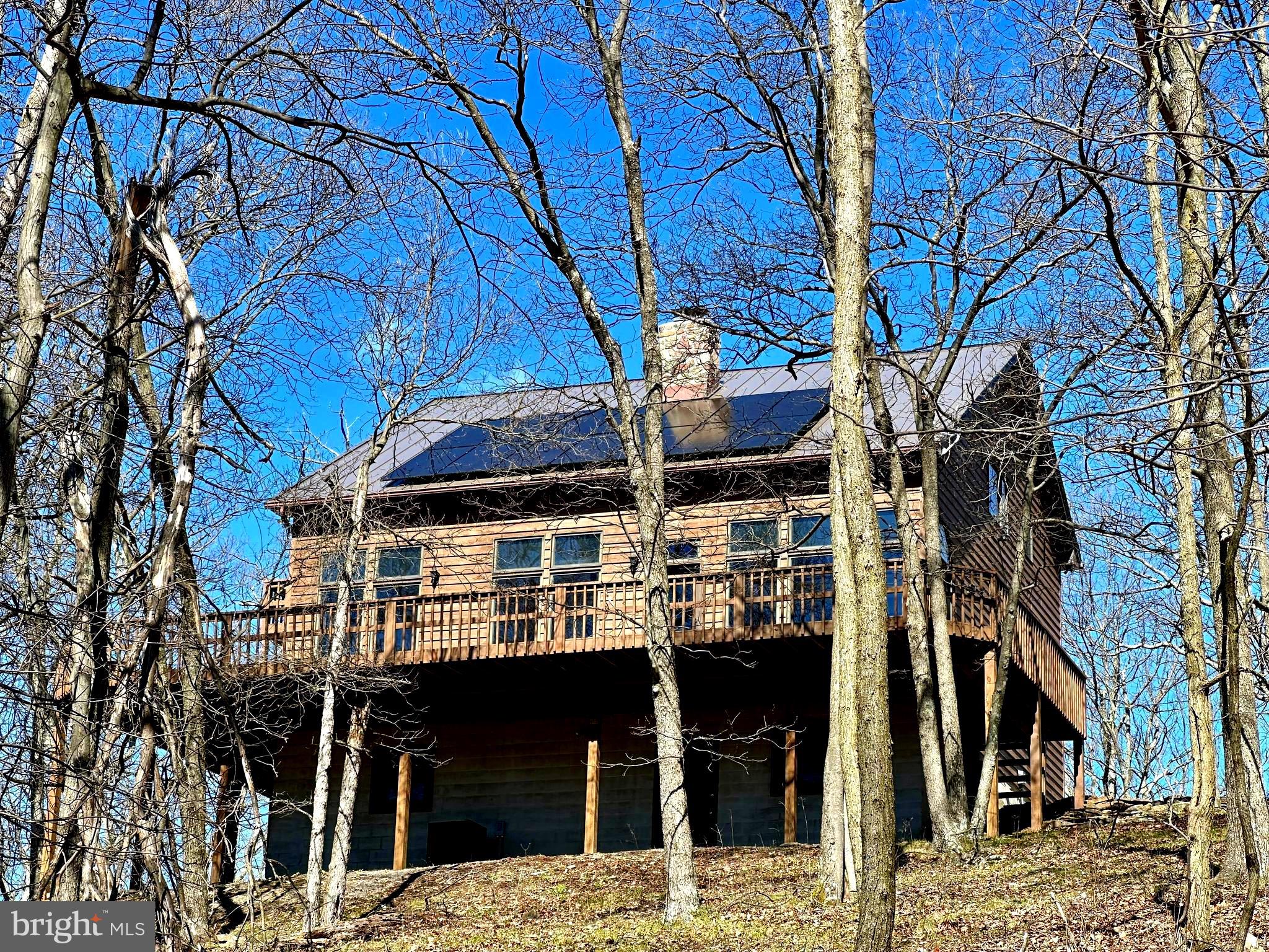 VIEWS & A Beautiful Wrap Around Porch To Enjoy Them! This Gorgeous Cabin sits in the Beautiful West Virginia Mountains! When you have views this wonderful you want a home that accentuates them and this home does just that. Inside this Cedar sided Home you will find NEW Stainless Appliances, Cathedral Ceilings, Open Floor Plan,  a Stone Wood Burning Stove and an abundance of oversized windows that allow for Endless Views. The Open Concept Kitchen, Dining & Living is perfect for entertaining & everyday functionality. Main level Bedroom and full bath complete the living space.  Just off the foyer is a screened in porch perfect for bug free summers and watching and listening to the sounds of nature.  Watch the seasons change on the mountain as the fall foliage begins to paint the mountain side with its beautiful colors, during the summer enjoy the community lake and in the winter cozy up to the Stone Wood Burning Fireplace. Upstairs is a loft space with room for a sitting or office area. Also upstairs is the primary Bedroom & Bath with walk in Closet and cathedral ceilings.  Access to a private balcony for enjoying your morning coffee or nightcap beverage.  This floor is the perfect escape suite.  The basement has an abundance of unfinished bonus space just waiting to be converted into additional living space.   On this level you will find the heating & cooling system, laundry room complete with a laundry chute & a one car garage. The property's Solar System reduces the utility costs at this home.  From the lower level you can walk out onto the lower patio that has a sitting area and beautiful woodland views. From here you can go exploring on the walking trails that meander through the land. The Cabin sits on Over 11 Wooded Acres that offer privacy and adventure! The Preserve at New Creek Lake is a Gated community & permanent protection of nature, Adjoins 500-ac Community Conservancy Area w/miles of hiking trails. The Preserve adjoins 40-ac New Creek Lake.Convenient to Local Amenities, Ski Resorts, Seneca Rocks, Dolly Sods, Vepco Lake, Fishing and the National Forest. Call the mountains HOME, don't miss out on the peace and serenity this cabin offers!  It's a preserve, No Hunting allowed. Click The Camera Icon To Take A Virtual Tour & Call Today For A Showing!