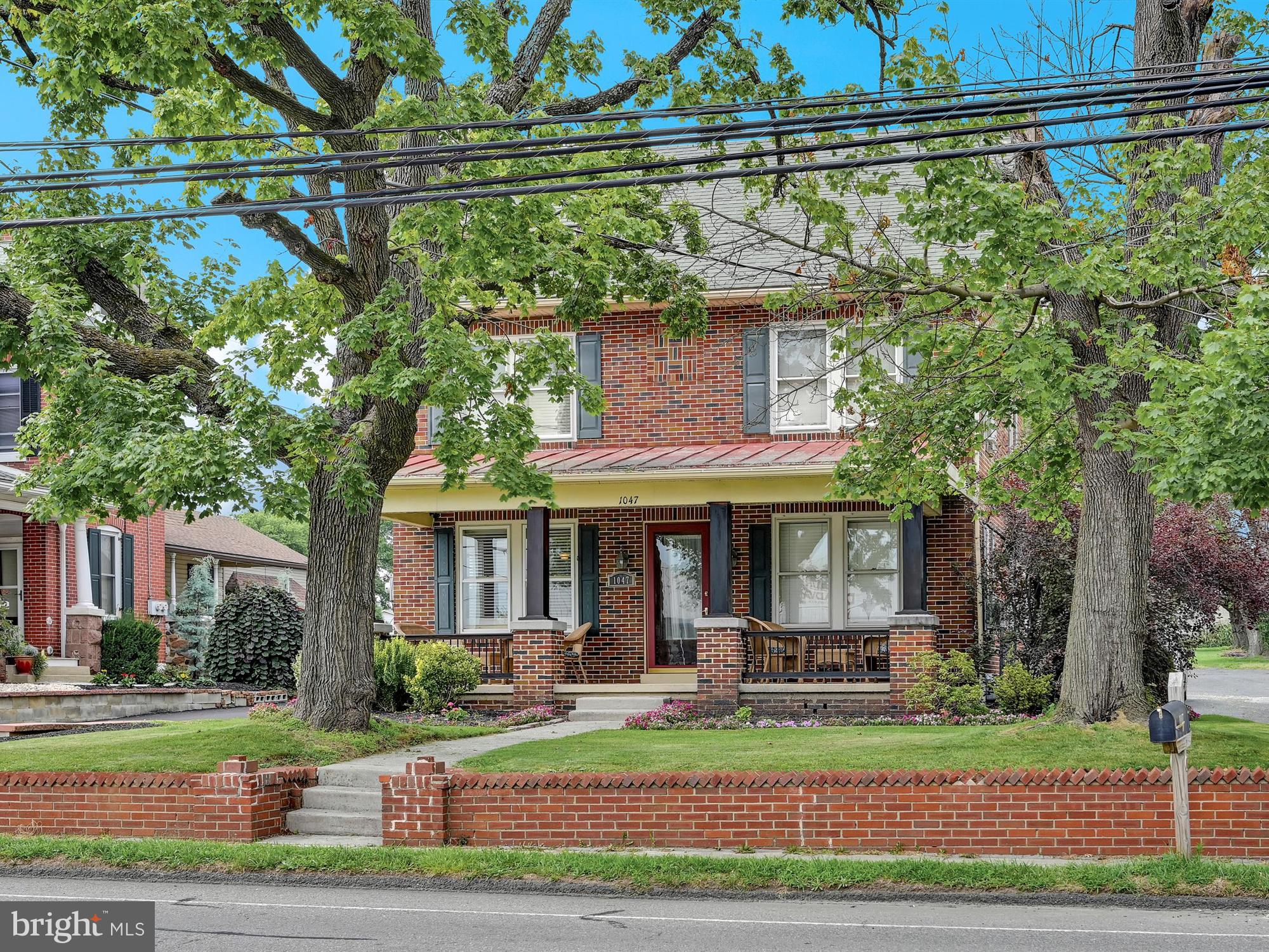 Stately brick home with a large covered full front porch.  New cherry kitchen with stainless steel appliances, new flooring, formal dining room with hardwood floors and french doors leading to living room area which boasts a stately open staircase in center of home filling this space with character and charm.   1/2 bath on first floor, bonus room off of kitchen is a 3-season room, currently used as a craft room. Finished lower level with knotty pine paneling and wall to wall carpet.  Utility room off of family room for storage.  Full walk up attic.  Deck for entertaining and a detached two car garage with wood stove.  This home is a must see!