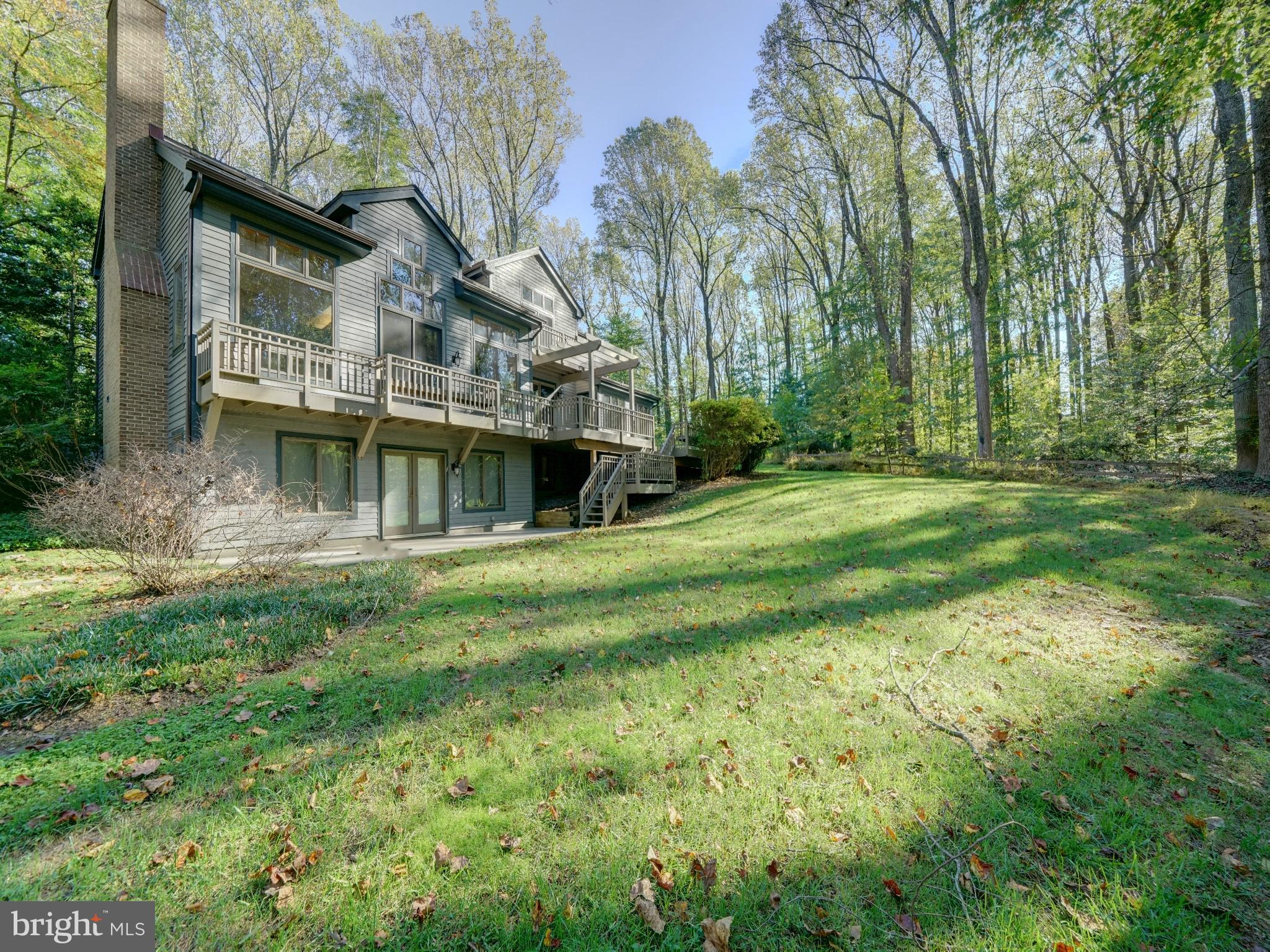 Spectacular custom built post and beam home built with a combination of beautiful woods including California Redwood and Western red cedar. Sitting atop a wooded 3+acre lot, the majestic mature trees have provided a quiet shelter of privacy for this spacious home. The green hillside and garden areas are surprisingly sunny, as the sun peers through the treetops. The front entryway has soothing ponds with fountains along the paved walkway to the front porch. The home has over 5500 sq ft inside with almost 5000 sq ft finished on 4 levels. Total of 5 bedrooms 3.5 baths, the open floor plan has soaring 2 story wood ceilings, skylights, and a full back wall of oversized windows with incredible views. Enjoy all 4 seasons peering out at the rolling hillside and watch wildlife in its natural setting. Birds including woodpeckers, owls, blue heron, hawks and plenty of deer and fox are frequent visitors. Cozy up to the fireplace in the main level great room or the woodstove in the lower level rec room, both providing ambiance and warmth to the home. The first floor offers a perfect home office wing complete with a private bathroom. The great room has built ins and plenty of natural light that flows through to the dining room and kitchen. Off the kitchen is a sunroom with windows on all sides. 1st floor mudroom with access to the 2 car garage from the main level or from the garret on the second level. The wood deck is the entire rear of the home with built in benches and pergola. The lower level is daylit with it's own exit that leads to an added driveway for convenience for guests during their stay. There is a guest suite with bedroom, full bath, kitchenette in addition to the huge rec room/gaming room combination. Plenty of storage in addition to the finished area. Upstairs the thoughtful design has included bedrooms with lofts, guest bath, access to the upper attic, bedroom level laundry room with washer/dryer and the primary suite. The primary en suite bath has many designer touches as expected in a custom built home including double vanity, soaking tub and separate tiled shower. The bedroom is spacious with an added sitting area. Adjoining the primary bath is access to the garret, space above the garage. The wood beam spans the entire length and has plenty of window light. There is a 2 person sauna, providing a relaxing escape in this hidden treasure space. There are 2 high energy efficient HVAC systems, newer hot water heater, all replaced within the past year. There is a  whole house generator in case of emergency and gutter helmets. The home sits back off the main road with a shared driveway that ends where the private circular driveway and extended driveway meet. Plenty of room for parking. Clarksville has a wonderful town center with large community center with shopping, dining and recreational features. Downtown Columbia and Historic Ellicott City are only a short drive away. Convenient to major Routes 32, I70 and Rt 29, perfect commuter community with easy drive to Baltimore or Washington suburbs and the BWI business district. John Hopkins Howard County Medical Center, JHUAPL and Ft Meade/NSA are just a few of the employment centers close by. Howard County parks, recreation and schools are all highly desired. This home is a wonderful choice, offering a unique design, serene setting yet so convenient.  Call your agent to set up a private tour.