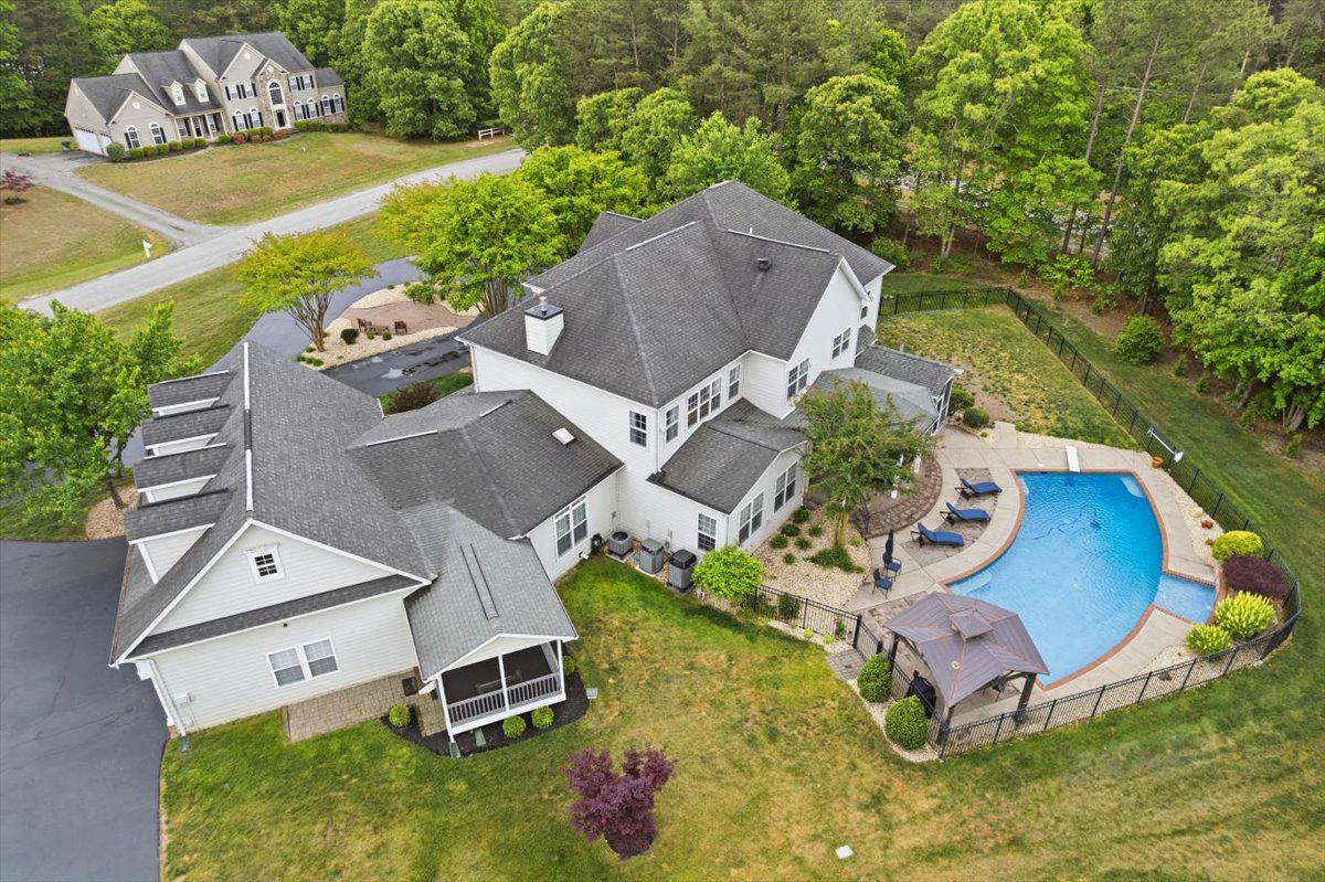 CONVENIENCE AND MOVE-IN READY  estate home with resort-style backyard + extensive workshop and garage space on 2 Private Acres. Welcome to this exceptional custom-built 8,600+ SF estate designed for large-scale entertaining, multi-generational living and luxury everyday in the heart of mid-Calvert County. The location is within 10 minutes to Solomons Island, 5 minutes to Nan’s Cove boat launch. For car enthusiasts, hobbyists, contractors, small business owners, or anyone needing serious storage and workspace, the property includes two detached outbuildings with four additional garage bays, workshop space, water, electric, and slab foundations. The home itself has a thoughtfully designed main level, featuring a private guest wing with a separate entrance and private screened porch, independent yet still connected to the heart of the home. The expansive floorplan includes a gourmet eat-in kitchen, large dining room, an executive office with custom wood accent walls, spacious family room, a stunning morning room with soaring 12-foot ceilings and marble flooring. Hardwood floors span most of the main level. Upstairs, the luxurious owner’s retreat is gorgeous with tray ceilings, fireplace, coffee bar. Three additional oversized bedrooms and two full baths complete the upper level. The fully finished walk-up lower level was built for entertaining and flexible living, featuring a second full kitchen, media room, billiards area, built-in entertainment space, a fourth fireplace, and a full bath with a tiled shower—ideal for pool access, guest overflow, or separate lower-level living arrangements. The outdoor living space centers around a stunning 20'x40' heated pool with a tanning shelf, diving board, stone waterfall, and expansive patio spaces designed for unforgettable gatherings. Two oversized pavilions create the ultimate setup for outdoor entertaining, celebrations, cookouts, and summer weekends at home. A separate fenced pet area adds even more convenience. This is more than a home—it’s a rare opportunity to own a private family compound-style estate with luxury amenities, flexible living options, and unmatched entertaining potential. Home warranty conveys. Did we mention the incredibly low utility bills?