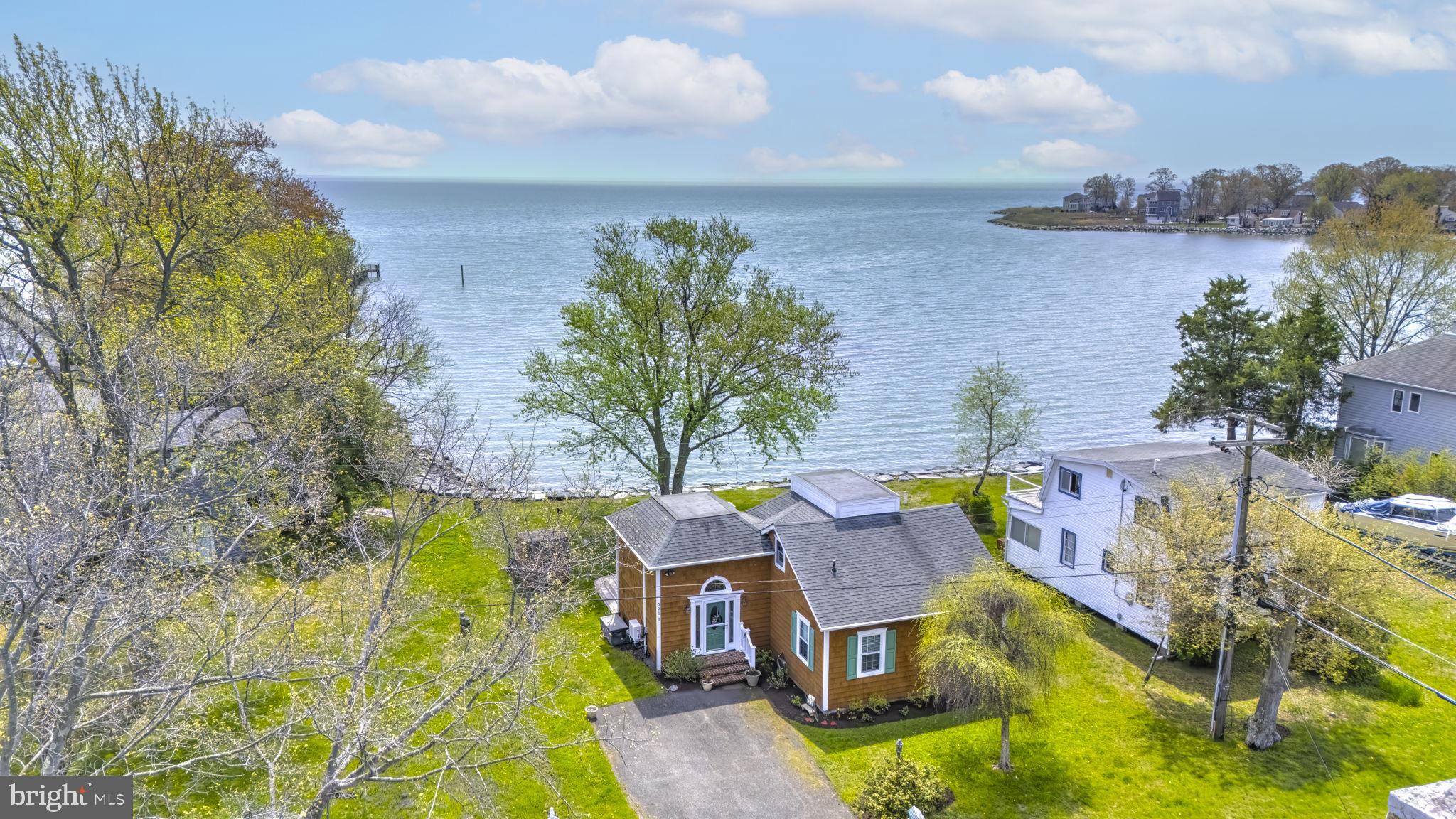 Non-riparian waterfront home offering sweeping, unobstructed views of the Chesapeake Bay. Wake each morning to breathtaking sunrises over the water, best enjoyed from your expansive deck with a cup of coffee in hand—an experience that never gets old. Inside, the home is filled with natural light and features an open-concept layout designed to maximize those stunning bay views. The main level boasts hardwood floors throughout, along with two comfortable bedrooms and a full bath. Upstairs, a versatile loft space with a half bath is ideal for a home office, guest accommodations, or a quiet retreat. Located just steps from the community pier, boat ramp, and additional amenities, this property offers the perfect blend of relaxation and coastal living. Home is not in flood zone.