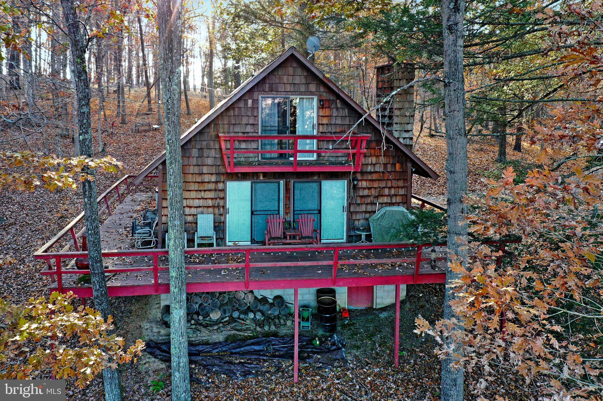 Cacapon River Access!! Situated on 5.34 Acres in gated communty, this well maintained cabin is the perfect get away from the business of the city. Open Living Room/Dining/Kitchen with stone woodburning fireplace.   Dining and Living room lead to a spacious wraparound deck.   1 bedroom and 1 bath on the main level, 2 bedroom and half bath on upper level.   Balcony off one of the bedrooms.  Beautiful mountain views.   Located in the locked gate community of River Ridge with access to a  pristine community park with stone BBQ's, picninc tables, storage racks for kayaks/canoes, access to the Cacapon River for floating in a canoe, kayak or tube and bathroom facility on site.