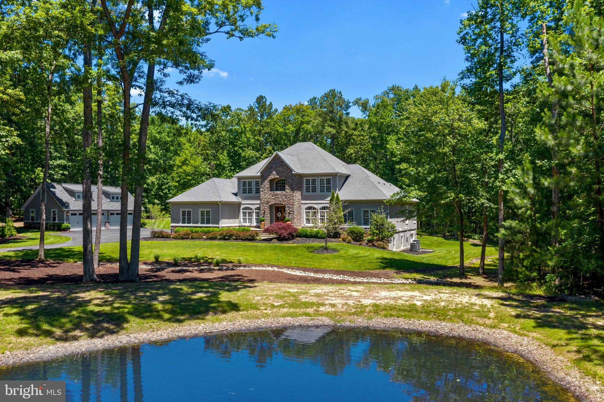 Extraordinary Dream Estate Home with private pond nestled on 7+ wooded Acres in the prestigious Fawn Lake Community! This Architectural Masterpiece has been carefully curated with timeless finishes and details designed for impressive entertaining, and casual everyday living within a resort-like Oasis. Boasting exceptional privacy, mature trees frame the stately entrance with a long meandering driveway that leads to this exceptional custom dream home with a stunning stacked stone facade and welcoming entryway with double Mahogany doors. A soaring two story elegant Foyer and Walnut hardwood floors set the stage from the moment you step through the front door. The Living Room features a beautiful stacked stone Fireplace anchored by built-in bookshelves and a wall of sliding glass doors leading to the expansive deck and the backyard Oasis. The Gourmet Kitchen is a chef's dream, complete with white cabinetry, professional stainless appliances to include a Wolf 6 burner Range, pot filler, massive center island with extra prep sink and Granite countertops, flows into a sunlight Breakfast Room, and a quaint Sitting Room with sliding doors granting access to the Deck and a covered Veranda with beautiful tongue and groove wooden ceiling and Flagstone floors. 
A large Formal Dining Room with exquisite details and large windows offers a perfect backdrop for formal gatherings. A Gorgeous private Office with custom built-in credenza and bookcases, features an incredible stone accent wall!  A private retreat of your dreams, the gracious main level Owner's Suite offers a luxurious Spa Bath with slipper tub, large tile shower, and dual vanities. A fabulous dressing room features an incredible dream closet with ultimate wardrobe organization. A Wet Bar with coffee station, plus private access to the backyard makes this an ultimate true sanctuary where you can relax and unwind.  The upper level boasts two Bedroom Suites with walk-in closets, sharing a large Full Bath featuring individual vanities.  A spacious loft area, plus two additional gracious Bedrooms with walk-in closets, and a Full Bath. 
Designed for entertaining, the lower level with Niles speaker system, features an amazing Recreation Room with a second Kitchen and Wet Bar, State of the Art Theater with 12 reclining leather chairs and 72" screen, plus a beautiful sunlight Great Room.  A cozy Lounge with accent wall, display shelves, bar height live edge counter, and wine storage, features a cool Sauna! A Spacious Bedroom with large windows and walk-in closet, an adjoining luxury Full Bath, plus a storage room completes the walk-out basement. In addition to the attached 3-Car Garage, this property is equipped with a separate detached 4-Car Garage that includes an incredible studio Apartment with full Bath above! 
Immersed in privacy, the incredible backyard features a massive Azek deck spanning the rear of the home surrounded by mature hardwoods and lush landscaping offering an exceptional tranquil outdoor space. A spectacular stacked stone Bar with wrap-around seating and built-in BBQ grill, plus the Veranda offer an ideal environment for relaxing, alfresco dining, and entertaining.  A scenic Pond with an ornamental fountain blends seamlessly with the landscape and creates a focal point in the idyllic setting. The property is equipped with a private 150 ft deep well for the pond and the lawn Irrigation system! Located within the gates of Fawn Lake, this spectacular turn-key custom Dream Home, sited in the exclusive Honor Bridge Estates section, is a true sanctuary providing the perfect harmony of the luxury, yet casual indoor and tranquil outdoor living you've been dreaming of! 
The gated Fawn Lake Luxury Community offers amazing amenities such as a boating recreational lake, beach, golf course, tennis courts, soccer & ball fields, dog park, volleyball courts, walking trails, Club House, marina, fitness center, restaurants, Country Club, playgrounds, and so much more!