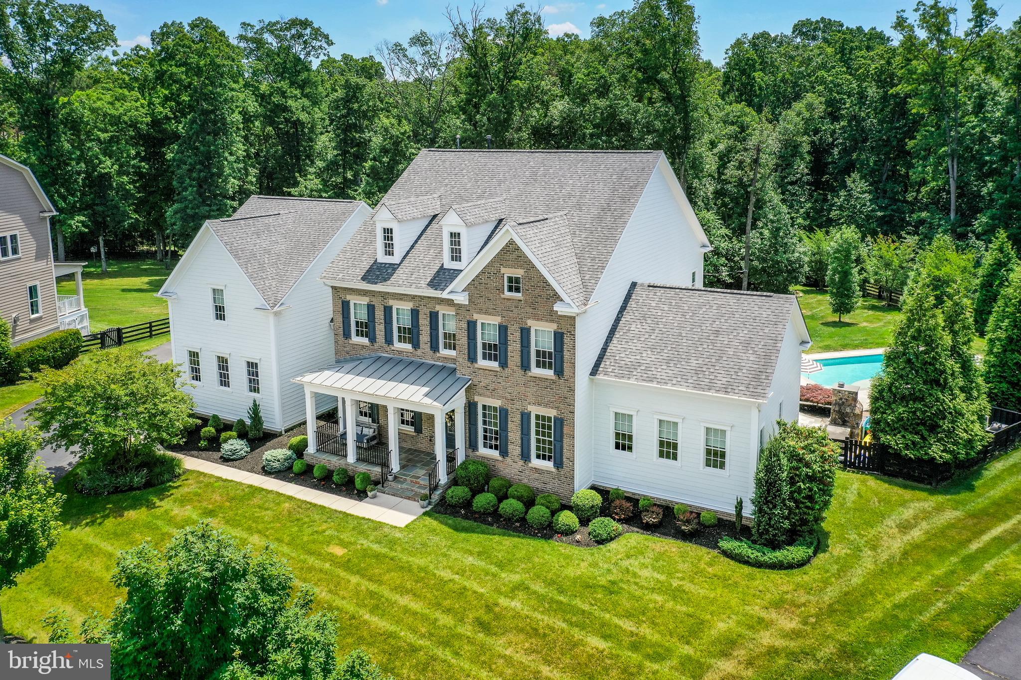 Welcome to this exquisite home, designed to impress with luxurious features and stunning craftsmanship. Don't miss out on this extraordinary 7,750 sq ft home (over 8,000 if you include the All Seasons Room), nestled on a .99-acre lot in the prestigious Willowsford Grant community, which offers an unparalleled living experience. Boasting 5 spacious bedrooms, 6.5  bathrooms,  4.5 car garage, and an in-ground pool, this property is designed for both elegance and comfort. 
Upon entering the home, the first floor features an inviting foyer with Brand New Floors (New Floors throughout the first floor, and second floor landing/hallway). To the right, you'll walk through French doors to a custom office with built-ins and crown molding.  To the left is your formal dining room that includes crown molding, wainscoating, and a decorative ceiling.   The gourmet kitchen is equipped with top-of-the-line Wolf cooktop stove, stainless steel appliances, marble countertops, an oversized island, and a cozy eat-in area with a gas fireplace surrounded by natural wood accents. The kitchen is open to your spacious family room that includes a decorative coffered ceiling and fireplace surrounded by stone.  The all-season room, complete with a fireplace, oversized fan, a serving area, and overhead heaters, extends your living space year-round.  The first floor also includes a magnificent in-law suite with a walk-in closet and attached full bath. 
 
The second floor includes a serene primary suite with an enlarged, custom walk-in closet with island, and a spa-like bathroom with soaking tub and stand-up shower with multiple shower heads.   You could also relax in the primary bedroom's sitting area, or on the covered balcony that overlooks the back yard.  You will also find three additional bedrooms on the second floor, each with walk-in closets, ceiling fans,  and en-suite bathrooms.   To make things convenient, the spacious laundry room with utility sink is centrally located to all the bedrooms.
The 2,000 sq ft finished basement offers a full bar with refrigerator and ice maker, home gym,  workshop, and full bathroom.   There is plenty of space to customize this finished basement to suit your needs.  
Outside, you’ll find a true oasis with an in-ground pool, a covered porch, a firepit with copper fire bowls, and a fully equipped outdoor kitchen. Your outdoor kitchen even includes a woodfire pizza oven.  Backing onto scenic woods and direct access to neighborhood trails, the property also features extensive landscaping, a vegetable garden, and a fully refinished pool with new heater and tiles. This home blends luxury, convenience, and natural beauty in one perfect package.