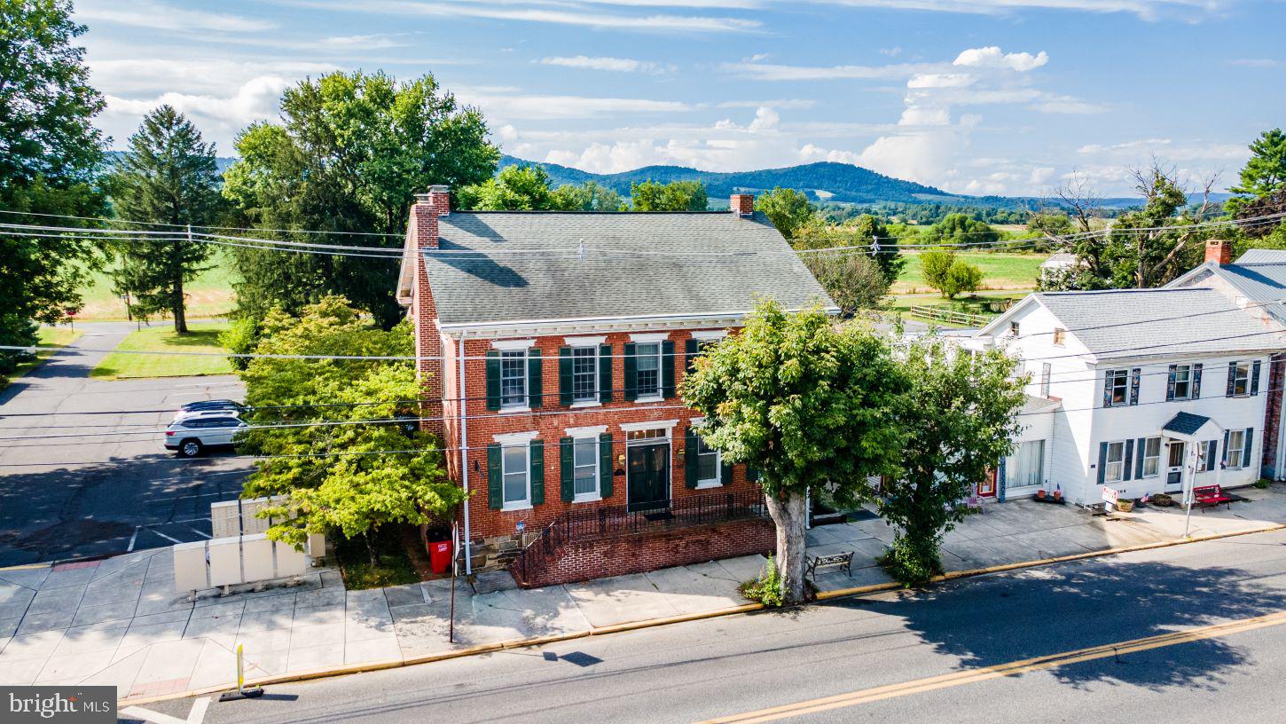 Spectacular pre-civil war home circa 1850, complete with the official plaque on the front of the home, is perfect and approved for an Airbnb, with its perfect location being a bonus!  This home has a vast amount of history within its walls starting with the builder being the one of the Musselman brothers who are also known for their applesauce.   This property is zoned both residential and commercial, with 5,000 + square feet,  making the possibilities endless.  Enter the home and step back into an era gone by; full of tons of character and charm, but loaded with all of the updates and modern day conveniences you would want.  The stunning hardwood floors in the foyer carry throughout the 1st floor, and the open staircase and chandelier will warm your heart.  The living room on the left has a wood burning fireplace and leads you to the stunning, updated kitchen.  The kitchen has exposed beams, quartz counter tops, a big island with slide in gas range, pot holder, and a built in desk and big pantry cabinet.  The formal dining room will come in handy for the upcoming holiday parties.  1st floor bedroom features  Indian  shutters on the windows which completely darken the room, and a full bath makes this great as a primary or guest area.  Upstairs, there are 3 bedrooms and 2 full baths. There is another bedroom above the summer kitchen!  The garage is accessible from the main house and the 2nd floor is currently being used a rec room and this is also where the 4th full bathroom is located.  This home also features upper and lower porches in the back of the home.  The yard is beautifully landscaped and has planters boxes already set up.  This one of kind home is one that you do not want to miss!